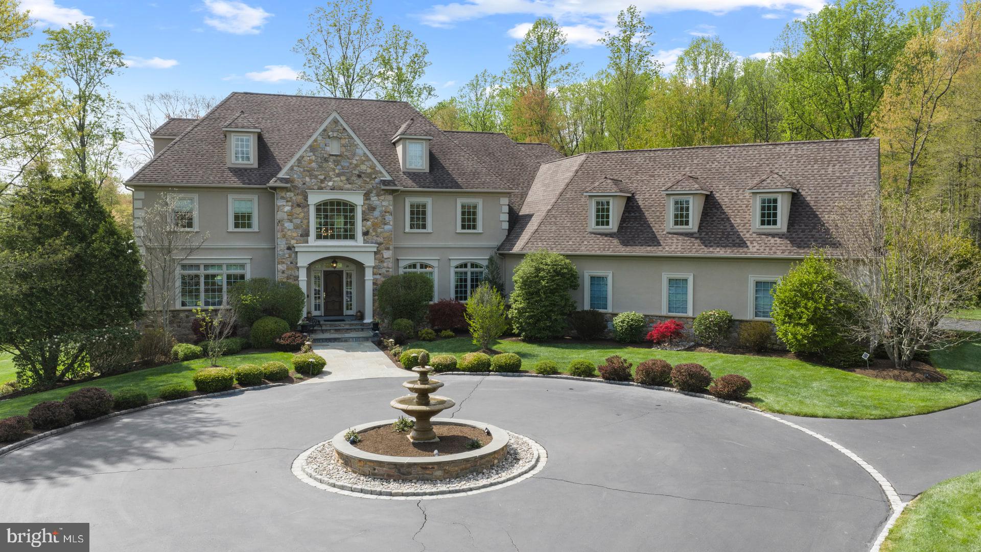 Experience exceptional luxury on 4+ acres in one of Solebury Township’s most coveted enclaves. Ideally positioned on a cul-de-sac, this custom-built Bucks County estate offers a rare combination of acreage, privacy, and architectural presence—introduced by a stately circular drive and fountain that set the tone for what lies beyond.

Step into the marble foyer with a gorgeous curved staircase and premium trim work.  Designed with both everyday living and elevated entertaining in mind, the chef’s kitchen features radiant heated floors, professional-grade stainless appliances, expansive granite surfaces, and an oversized center island with secondary dishwasher and refrigerated drawers. The dramatic 20+ foot high coffered family room is anchored by a stone wood-burning fireplace and framed by walls of windows overlooking a serene lawn and beautiful treed meadow beyond. Formal living room with gas fireplace, formal dining room, a butler’s pantry complete with wet bar, and a private office featuring custom built-ins and access to a wrap-around covered porch complete the main level.

Upstairs, the primary suite offers a true sense of retreat, with a spacious sitting area, dual walk-in closets, tray ceilings, and a separate flex space ideal for a custom walk-in closet, gym, or perhaps a large second floor laundry room. The spa-inspired bath features a steam shower, jetted soaking tub, dual vanities, and radiant heated floors. Three additional ensuite bedrooms and a full third-floor princess suite provide comfort and privacy for family and guests.

The finished lower level is thoughtfully designed for entertainment, featuring a pub-style bar, gaming area, a dedicated home theater with projection and surround sound, along with another bonus room, a full bath, and a large workshop. And its wall of windows and connection to the backyard do not disappoint.

Outdoors, the 4.25 acres offer endless potential, with ample space for a future pool and outdoor kitchen, complemented by patios and a wrap-around covered porch. Additional amenities include a generator, an alarm system, and a heated 4+ car garage with premium SwissTraxx flooring, many cabinets and shelves, and stairs leading directly to the basement.

Located within the award-winning New Hope–Solebury School District and just minutes from the vibrant rivertowns of New Hope and Lambertville—with convenient access to New York, New Jersey, and Philadelphia—this property represents a rare opportunity to own a private estate of this scale and caliber in the heart of Bucks County.
