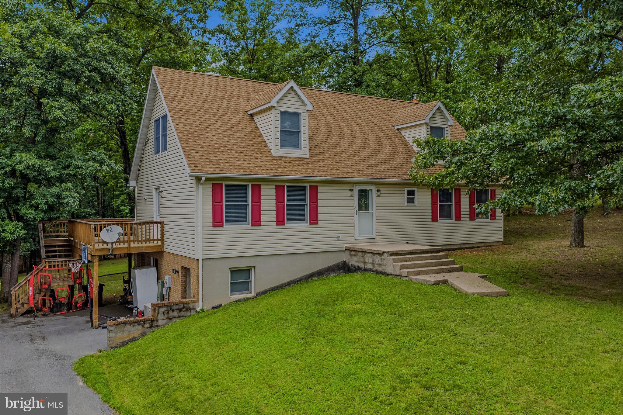 Welcome to 74 Key Acres Drive, a spacious 4-bedroom, 3-bath Cape Cod nestled on a generous 0.76-acre lot. Located just inside the Key Acres subdivision off Fairview Drive, this home offers the perfect balance of peaceful living and convenience—just minutes from downtown Berkeley Springs, where you'll enjoy charming shops, restaurants, spas, Berkeley Springs State Park, and easy access to I-70 for commuters.
Step inside to a welcoming living room that flows seamlessly into the expansive kitchen and dining area, creating an ideal space for everyday living and entertaining. The kitchen features a center island, updated appliances, and ample room for gathering with family and friends. Sliding glass doors off the dining area lead to a large rear deck overlooking the spacious backyard, which backs to mature trees for added privacy and a tranquil setting. The main level also includes a comfortable primary suite with a walk-in closet and private bath featuring a beautifully tiled walk-in shower. An additional bedroom and full bath on the main floor provide flexibility for guests or one-level living. Upstairs, you'll find two generously sized bedrooms—one with a walk-in closet—a full bathroom, a cozy sitting area, and two convenient storage closets. The walkout basement offers even more potential, featuring a one-car garage, laundry area, wood stove, and an existing mini-split system on one side, adding the possibility to finish the space into additional living or recreational areas. Recent updates include a new cold-weather heat pump installed in December 2025, providing efficient, reliable heating and cooling for year-round comfort. With its spacious layout, private backyard, and excellent location, this home is ready to welcome its next owners. Schedule your private showing today and discover everything 74 Key Acres Drive has to offer!