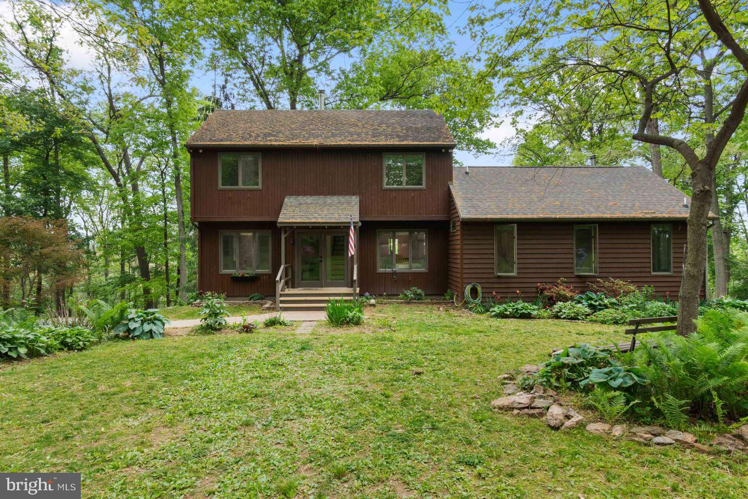 A custom-built, multi-generational home tucked into a country hillside — your own private retreat in the woods.
Drive up the fern-lined lane to a park-like setting with established perennial gardens, mature forest, blooming rhododendron, and wildlife around every tree.

Gather for breakfast in the sun-filled kitchen — breakfast bar, large windows, and sweeping views of the farmland in the valley below.

Relax on the expansive screened porch — listen for the drum of the red-headed woodpeckers, the chatter of squirrels, the distant hoot of a great horned owl.

Summer nights belong in the picnic spot in the woods, with its grill, porch swing and the fireflies coming out at dusk. In winter, settle in by the woodstove in the living room, and watch the snow fall quietly on the hilltop.

The enormous main-level primary suite features its own woodstove, vaulted ceiling, and sunny bath — a true sanctuary. Upstairs: three bedrooms and a full bath. Downstairs: a spacious family room. AND — a fully self-contained studio apartment with its own private entrance. Full kitchen, full bath, and room for both living and sleeping. Perfect as a rental, in-law suite, or au pair space.

Outside: a shed, chicken coop & run, tool room, storage room, zip line and swing in the woods — and attic storage throughout.

Some homes you inhabit. In this one you enjoy the life you live.