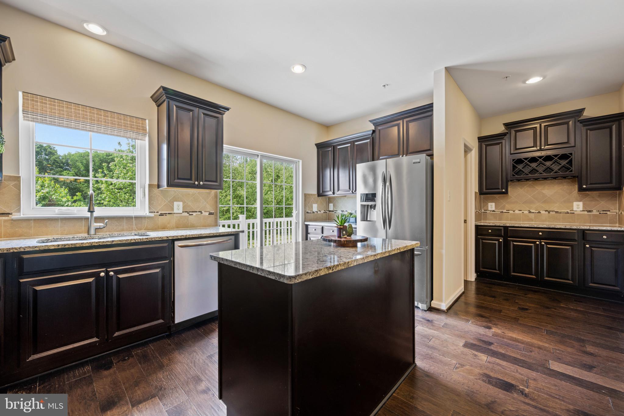 Welcome home to this breathtaking 4-level townhome in the highly sought-after Oxford Square community of Howard County! As the coveted Lennar "Ellicott" model, this is the largest and most desirable layout in the neighborhood, boasting nearly 3,000 square feet of luxurious living space (Note: public records do not reflect the expansive 4th-level loft!). Situated on a premium lot backing to serene trees and directly on the community walking paths, this 3-bedroom, 3-full, and 2-half-bath home is an absolute showstopper. Step through the front door into the welcoming entry and mudroom area. This lower level features a versatile, open recreational space, a full bathroom, and convenient access to your spacious 2-car garage. Head upstairs to a spectacular, sun-drenched main living level designed for entertaining. The oversized gourmet kitchen is a chef’s dream, featuring endless granite countertops, a massive center island, a walk-in pantry, and dedicated wine bar and coffee stations! The kitchen flows seamlessly into the dining space and an expansive living room wrapped in windows for abundant natural light. A convenient half-bath is also on this level. Step through the glass slider doors onto your first private deck—the perfect, secluded oasis for grilling and al fresco dining while overlooking the peaceful tree line. The third level is dedicated to comfort, featuring three generous bedrooms, two full bathrooms, and a convenient bedroom-level laundry area with a full-sized washer and dryer. The luxurious primary suite boasts a large walk-in closet and a spa-like en-suite bathroom with dual-vanity sinks and a spacious shower. The crowning jewel of this home is the incredible 4th-floor loft! Complete with its own half bathroom, this massive space is perfect for a home theater, "man cave," playroom, or private retreat. It opens up to a second private, rooftop-style deck offering gorgeous, elevated views of nature. Living in Oxford Square is a lifestyle. Enjoy resort-style amenities including an outdoor pool with a fireplace and patio, a state-of-the-art fitness center with locker rooms, and an upscale community clubhouse. The clubhouse features multiple meeting rooms with fireplaces, a children's playroom, and a stunning banquet room available for private events—it's also a perfect quiet escape if you work from home! Step out your back door directly onto the community jogging paths or take a short stroll to the community shopping center for a treat at Clock Tower Coffee & Bakery, the hair salon, or Little Eggs Daycare. Zoned for Howard County's newest, state-of-the-art schools: Hanover Hills Elementary, Thomas Viaduct Middle, and the brand-new Guilford Park High School (all LEED Silver or Gold certified!).  A true commuter's paradise, you are just minutes from major routes and BWI Airport. Best of all, the community offers a complimentary Uber to the Dorsey MARC/Amtrak train line located just minutes away!  Don't miss your chance to own the premier home in Hanover's best community. Schedule your tour today!