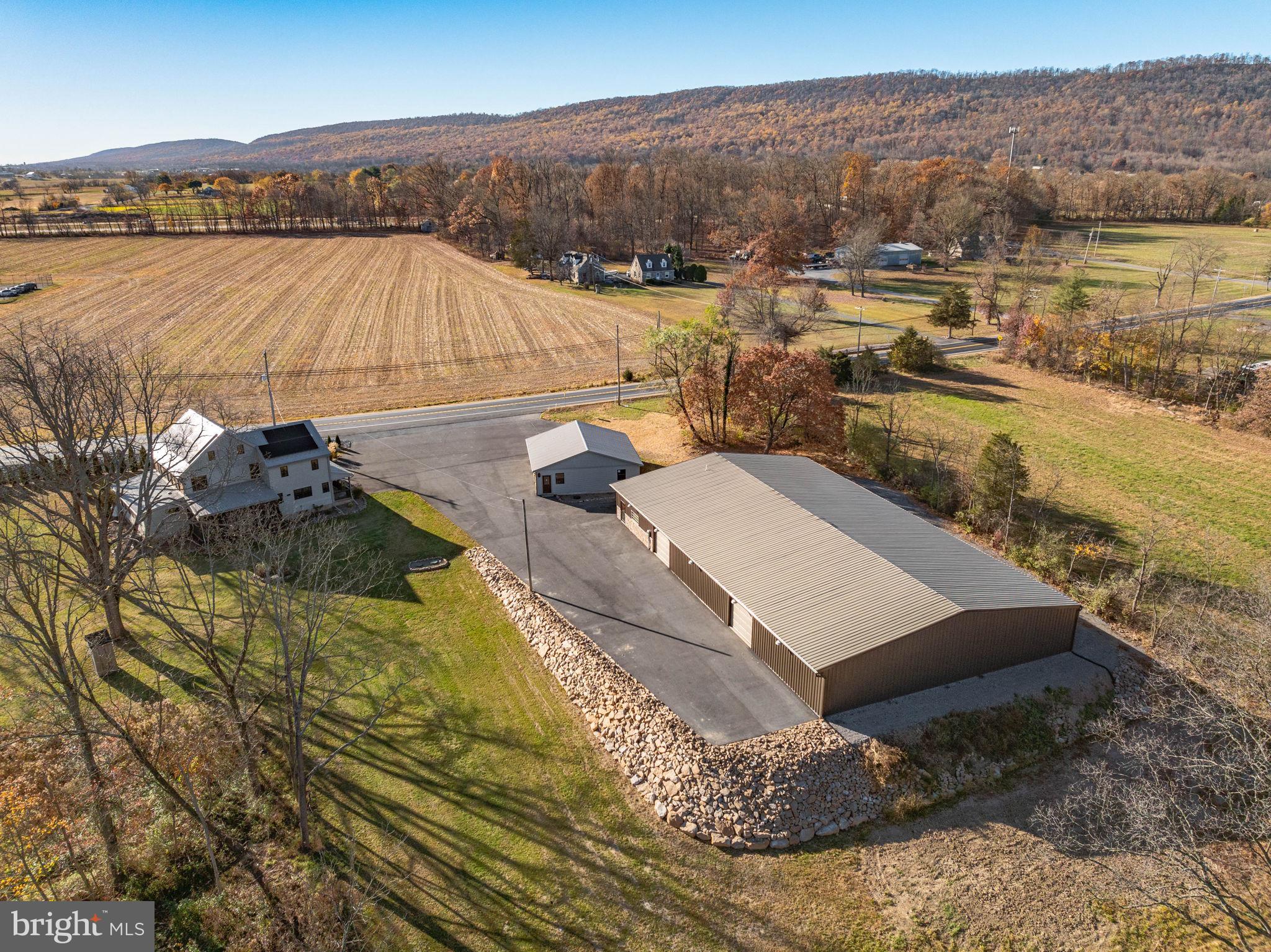 This rare and beautifully renovated 3-story American Chestnut log home, dating back to the early 1800s, offers a unique blend of historic charm and modern amenities with the endless possibilities that comes with the dream car enthusiast's commercial garage. COMPLETELY renovated in 2017, the home has been updated inside and out, preserving its original character while incorporating all the conveniences of contemporary living. Situated on a sprawling property that borders state game lands and a rail trail, the home is perfect for those seeking a peaceful retreat with easy access to outdoor recreation, including excellent hunting opportunities.

The interior of the home boasts exposed original beams with new chinking and new drywall, while the custom-made solid wood 42" Alder front door makes a stunning first impression. Inside, you’ll find a fully updated kitchen with Kraftmaid cabinets, quartz countertops, a center island, and high-end Samsung stainless steel appliances, as well as a custom-built wood 2-person desk and solid wood bookcases in the loft. The spacious living room with is enhanced by a new propane fireplace, adding warmth and comfort to the space. The home features a new on-demand propane water heating system, a new electrical panel and wiring, new plumbing with PEX tubing, new flooring, all-new windows, and solid wood interior doors throughout. The bathrooms have been completely updated with modern fixtures, including a luxurious new double tile shower and whirlpool double tub. The master suite features a walk-in closet, and there is ample closet space throughout the home, including huge closets on the first and second floors. For year-round enjoyment, the enclosed 3-season porch includes custom folding tinted blinds, providing a perfect spot to relax.

The home has been upgraded with modern systems, including a new central air and heating system, a new metal roof, and all-new siding for long-lasting durability. The two-year-old blacktop driveway leads to a newly remodeled 36' x 36' 3-car garage with commercial-grade electric wiring, new doors, and Genie openers. Adjacent to the home is a 120' x 70' commercial steel building with underground utilities, radiant floor heating, office space, utility rooms, a work area, a showroom, and a bathroom. Currently zoned for use as a state and township-approved classic car dealership, the building can be maintained for its current purpose or repurposed to fit the buyer's needs. The property is supplied by two working 1800s hand-dug wells, both updated with modern plumbing—one servicing the house and the other the commercial garage. The entire property offers incredible potential for residential or commercial use, with the flexibility to continue the current business operation or transform the space into something entirely new.

Conveniently located near I-81 and I-78, this home provides both privacy and accessibility, offering a rare opportunity to own a historic home with all the amenities and infrastructure needed for modern living. Whether you're looking for a unique residence or a versatile business space, this one-of-a-kind property is a must-see.