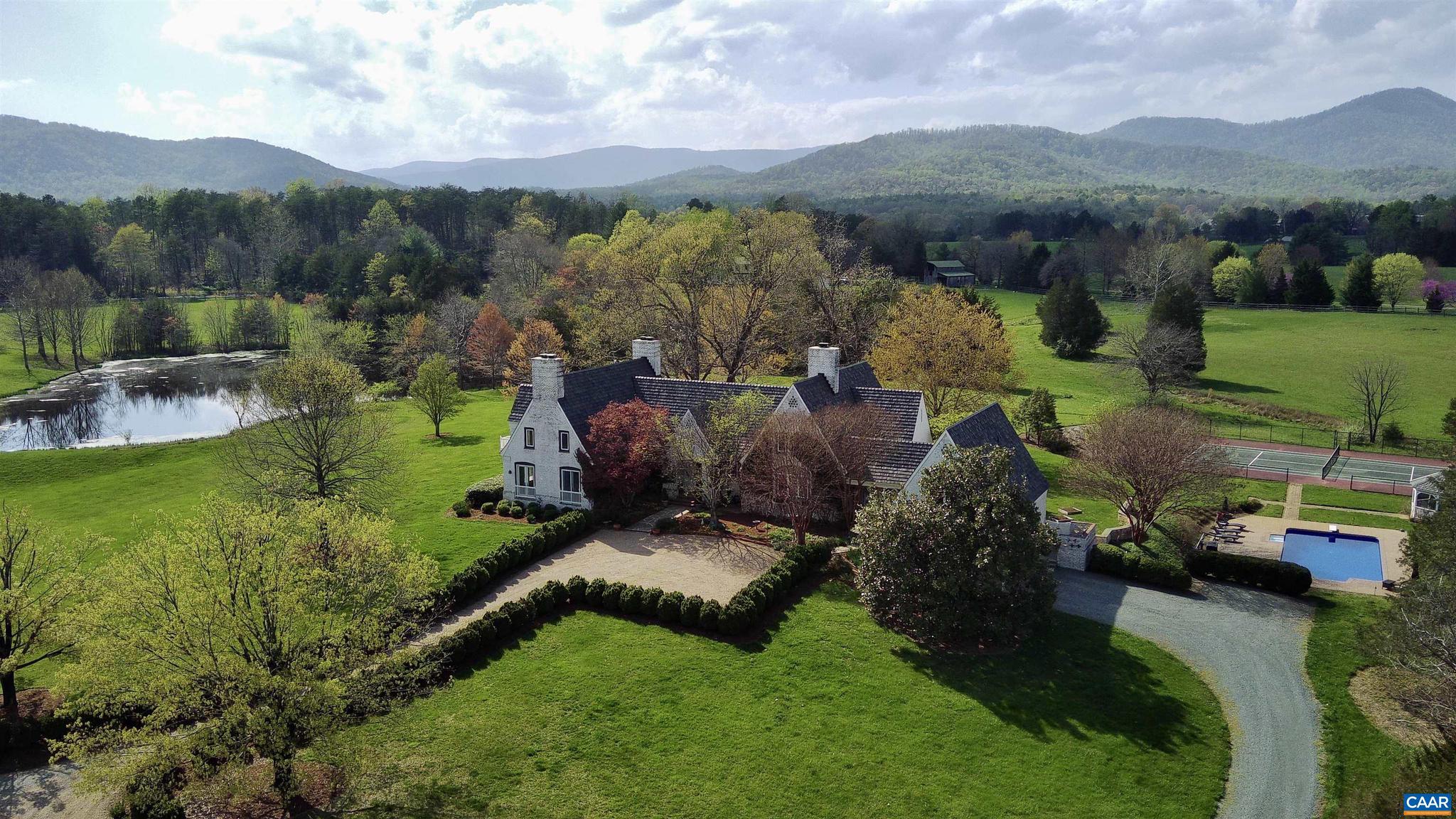 Drive under a Willow Oaks lined, canopied driveway, flanked by mountains, & enjoy the pond & pastoral views, leading to this magnificent English country estate home. Fall in love with picturesque walking trails around this unique wildlife rich property, which also features a pool, tennis/sport court, stream & barn. Entering the home, immediately fall in love with the bucolic views highlighted in the conservatory, featuring a blistered poplar wet bar. Spacious living areas with mountain views & access to private patios. The great room & kitchen feature soaring 20? ceilings, solid Cherry hardwood floors, & hand-hewn beams, reclaimed from a 200-year-old Virginia barn. Custom built fireplace was hand laid by a local artisan.� Enjoy a kitchen designed for function, family & entertaining featuring a 11-ft granite island, Wolf induction & gas cooktop, dual KitchenAid dishwashers, 48? refrigerator. Vintage, Venetian glass doors open to the wine cellar. 1st floor & 2nd level primary bedroom options. All bedrooms have ensuite baths with access to patios & balcony views. The guest wing has two bedrooms, kitchenette, and full bathroom. New composite roof. New pool liner & cover. Room for horses! Video tour and 3D tour links avail. by request.,Granite Counter,White Cabinets,Fireplace in Bedroom,Fireplace in Family Room,Fireplace in Kitchen