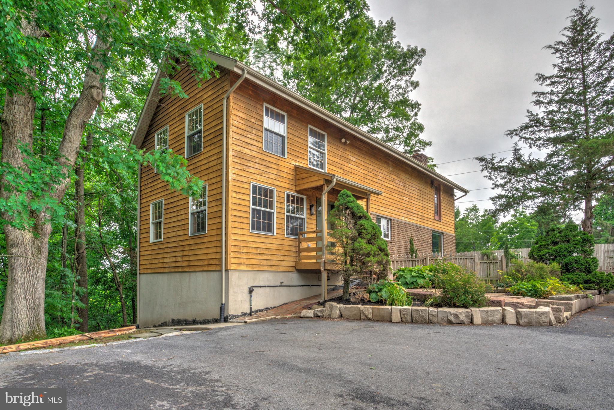 Nestled on a tranquil, partially-wooded lot over an acre in desirable Palmyra, this beautifully renovated 3 bedroom, 3.5 bathroom single-family home offers the perfect blend of rustic charm, modern comfort, and flexible living! With its unique cabin-style exterior, this property is equally suited as a full-time residence or an incredible private retreat getaway! A partial wraparound deck and covered screened-in porch create the perfect setting to relax and enjoy the peaceful outdoor surroundings. The massive detached 5-car garage with its own full bathroom offers endless possibilities for hobbies, workshop space, recreation, or storage. Inside, the warm and inviting interior showcases refinished hardwood flooring, wood-clad walls throughout, and an exceptional layout designed for both comfort and entertaining. The separate living/dining room flows into a stunning brand new kitchen featuring all new cabinetry, quartz countertops, stainless steel appliances, and an open connection to the spacious den highlighted by a dramatic stone fireplace and large, original wood beams. The newly added first-floor primary suite is a true retreat with lofted ceilings, abundant natural light, and a luxurious ensuite bath complete with a tiled tub/shower combination. Upstairs, you’ll find two additional oversized bedrooms, including one with its own fireplace, along with another full bathroom. The walkout lower level adds even more versatile living space with a cozy flex room centered around a third fireplace, a bright bonus room with comfortable carpeting, and an additional full bathroom. Additional upgrades include a brand new high-efficiency HVAC system and a recently inspected septic system that fully passed for added peace of mind. This one-of-a-kind property combines character, comfort, and versatility in a truly special setting — don’t miss your opportunity to make it yours!