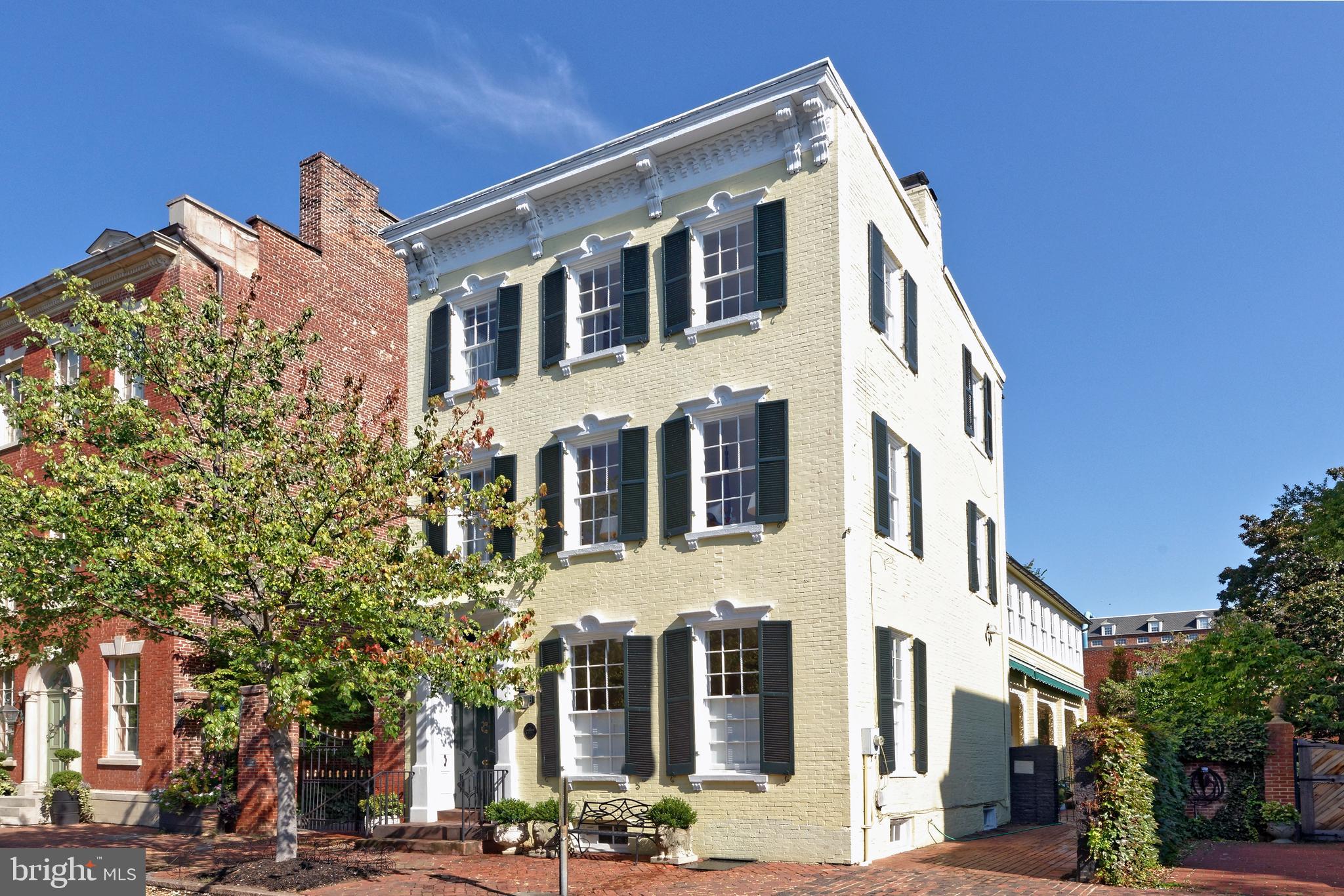 Nestled in the heart of Old Town, this magnificent Victorian residence exudes elegance and offers a unique opportunity to own a piece of history.  Built in 1870, this freestanding brick home sits on a beautiful tree-lined block and its picturesque façade with decorative window pediments and cornice add to the inviting curb appeal.  High ceilings, tall windows, original heart pine floors, 2 wood burning fireplaces, handsome millwork, and other fine details showcase the perfect blend of old-world craftsmanship with modern conveniences.

The multi-story interior is gracious and enchanting, introduced by a welcoming double door vestibule with marble flooring, spacious front hall with an original staircase and shadow rail, high ceilings, and an antique bell chandelier.  Gorgeous original 9’ double doors with hardware open to the generously proportioned living room with 10’5” ceilings where entertaining is effortless.  Natural light streams through tall windows on two sides with original folding shutters and a wood burning fireplace with an ornate mantle makes an elegant statement.  A wonderful formal dining room is a lovely setting for gatherings.  Delight the chef in the sunny kitchen equipped with new stainless appliances, a period fireplace, abundant cabinetry, decorative corner china cabinet, and access to the covered veranda.  Enjoy morning coffee or a casual meal in the triple windowed eat-in area overlooking the expansive brick patio.  Completing the main level is a convenient powder room to accommodate your guests.

The second level presents a generous family room, ideal for relaxing, with many windows and built-in bookshelves.  A delightful guest suite provides a comfortable setting for family or guests with a door to access to the fabulous sunroom. The light-filled primary suite is a private respite featuring a dressing room with large closets, custom built-ins, access to the bright sunroom, and an updated bath with seamless glass shower and marble vanity.  The third level offers two additional bedrooms, full bath, and a cedar closet. Other special features include a large lower level with built-in shelving, additional storage, and a laundry area with sink.

Savor the outdoors on the deep covered porch with intricate wrought iron embellishments or on the expansive patio garden retreat surrounded by mature trees and specimen plantings.  Outdoor enthusiasts will enjoy reading or relaxing in the gazebo or working in the potting shed.  One off-street parking space beyond the iron gate completes this important property..  This historic gem enjoys a prime location on one of Old Town’ sought-after streets, minutes to shops, restaurants, parks, and the Potomac River.  Now is the time to embrace the chance to create new memories in this remarkable residence.