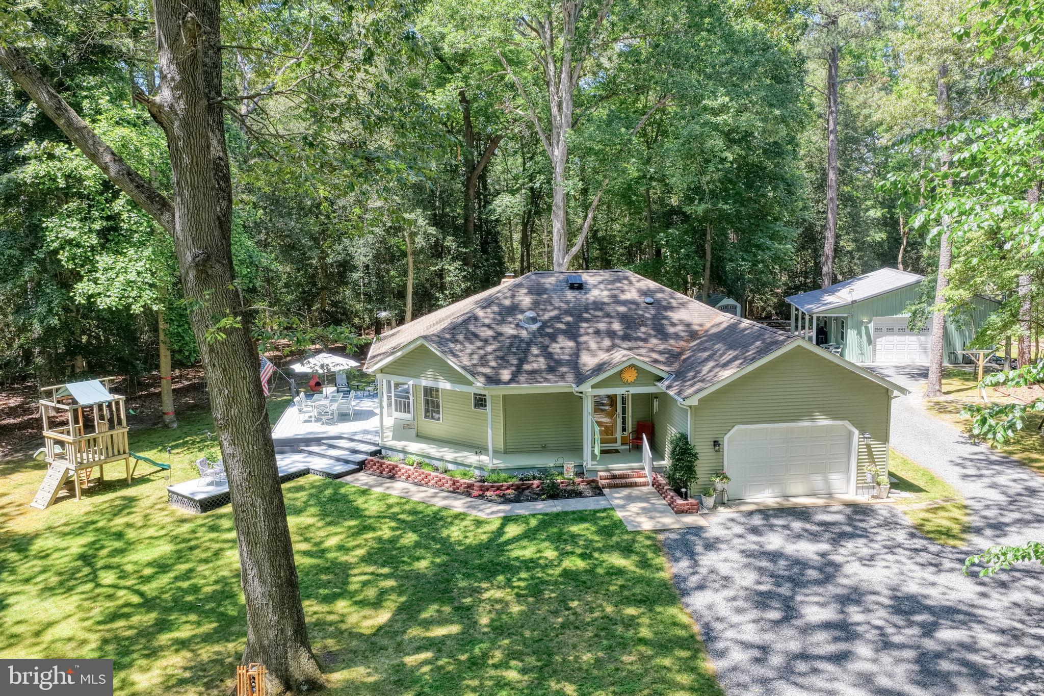 Nestled on a private, wooded 1.73-acre parcel off Zoar Road, welcome to 25399 Sturgis Ln. This charming 3-bedroom, 2-bath rancher, built in 2006, offers the perfect blend of privacy, comfort, and functionality. The kitchen features quartz countertops, glass tile backsplash, pantry, movable island, newer stainless steel gas range and refrigerator, and flows seamlessly into the open-concept living and dining areas. Sliding doors provide easy access to the expansive wraparound deck and screened porch, creating the perfect setting for entertaining guests or enjoying the peaceful wooded surroundings. The primary suite offers a walk-in closet and private ensuite bath with a stall shower, while two additional guest bedrooms share a full hall bath with a tub/shower combination. Cozy up by the electric pellet stove or relax outdoors with multiple decks, a screened porch, outdoor shower, and hot tub that conveys with the property. A standout feature is the impressive 24' x 24' outbuilding with a lean-to complete with electric, water, and wood stove—ideal for a workshop, hobby space, home business, or additional storage. There is also a separate shed for lawn equipment, pull-down attic storage, and ample parking space. The wooded lot provides exceptional privacy with endless possibilities, including room for a pool, equipment storage, gardening, or future expansion. Property includes well and septic with Class H inspection completed. Low utility costs with Delaware Electric Cooperative service provider. Conveniently located less than 15 miles from the Lewes & Rehoboth beaches, outlet shopping, and dining. This property offers the tranquility of country living with easy access to the Delaware coast. Lots of potential in a peaceful setting!