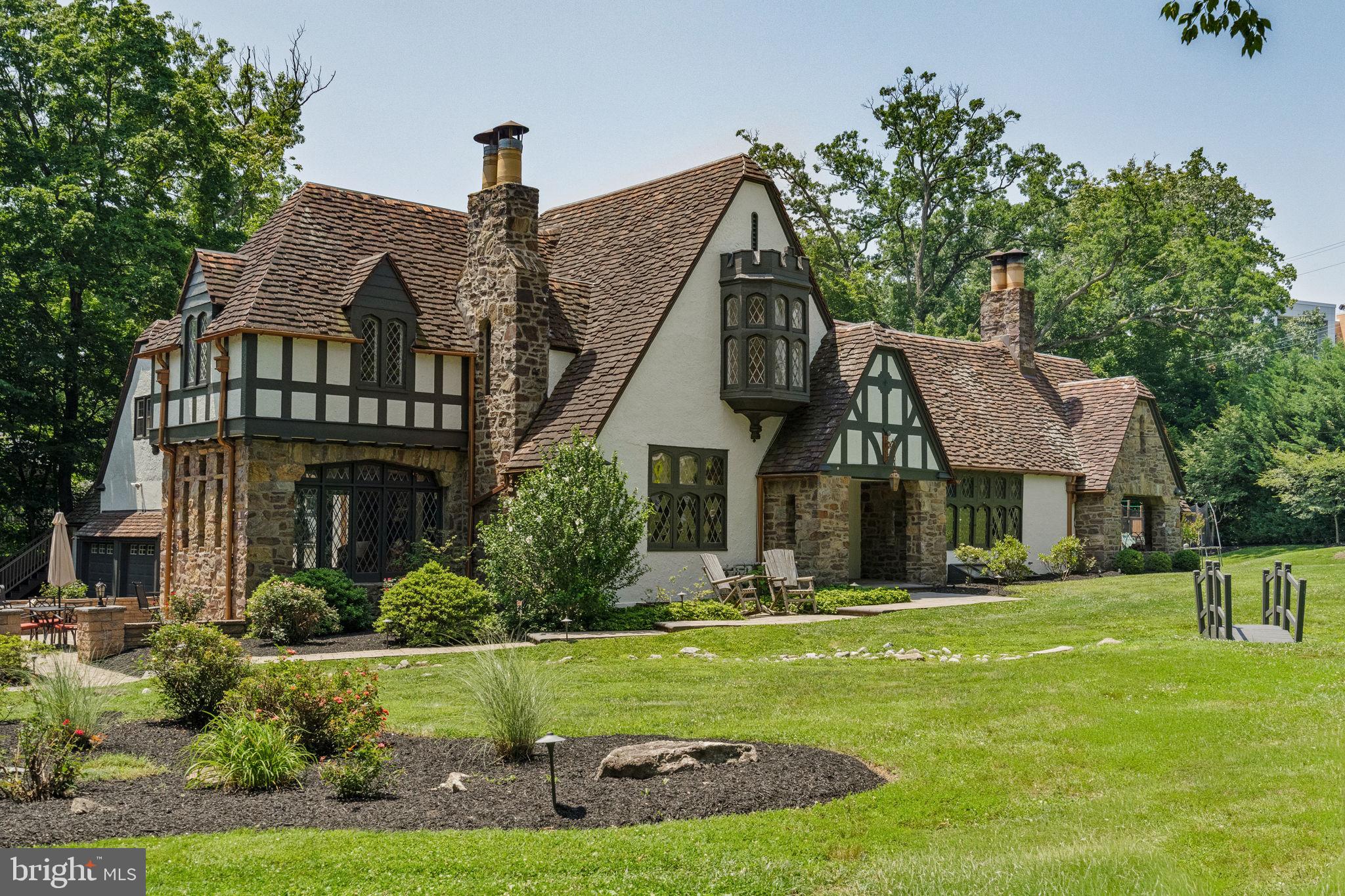 Here’s your chance to own “Tall Trees,” a rare & stunning home offering serenity & privacy in the sought-after Baederwood neighborhood in the A-rated Abington School District. Built in 1938 for the Laird & Schober Shoes family, the Christian Louboutin of their time. Laird & Schober Shoes was founded in Philadelphia in 1870 & became internationally renowned for crafting luxurious women's & children's footwear, winning the Grand Prize at the 1900 Paris Exposition. This beautifully updated home offers 5 bedrooms, 3 full baths, 2 half baths, a 3-car garage, an 8-car driveway, 3 working stone fireplaces, a foyer w/ a handcrafted staircase, a dramatic great room w/ soaring cathedral ceilings, exposed beams, expansive walls of glass, a fireplace & Juliet balcony, office/den, dining room, cook's kitchen w/ island & original butler's pantry, front & rear staircases, a finished lower level w/ a family/game/exercise room plus laundry, storage & workshop, & an above-garage Au Pair/In-Law Suite, home office or art studio w/ a kitchenette, 1/2 bath & private entrance. The outdoor living is equally impressive, featuring a heated in-ground Gunite saltwater pool w/ stone waterfalls, slide & spa, surrounded by travertine decking, an outdoor kitchen, fireplace, fire pit, covered porch, multiple patios w/ outdoor flat-screen TVs, trampoline, swing set, playhouse, basketball hoop, & a professionally landscaped, private, level & fenced yard. This home seamlessly blends preserved period craftsmanship w/ modern amenities for today's lifestyle. From the moment you enter, the defining architectural details reveal themselves: original hardwood floors, exceptional millwork & moldings, stile & rail paneled walls, soaring ceilings, handcrafted staircases & banisters, carved woodwork, leaded-glass casement windows & doors, stained-glass wood doors, crystal doorknobs, original sconces & light fixtures, & beautiful stonework. Nearly every room enjoys views of the surrounding gardens & mature landscaping. The exterior is equally exceptional. Travertine, bluestone & EP Henry patios, walls & walkways create a series of outdoor living spaces designed to engage w/ the landscape from nearly every angle. Updates include the entire interior & exterior having just been professionally painted, an updated kitchen & baths, windows, doors, garage doors & openers, roof, HVAC, high-efficiency Weil-McLain gas heater, Bryant high-velocity central air, Bradford White gas water heater, 200+ amp electric w/ multiple panels, hardwired house backup generator plug-in, light fixtures, ceiling fans, pool, spa, patios, walls, walkways, driveway, outdoor kitchen, fireplace, fire pit, landscape lighting, flower-bed irrigation, aluminum & wood fencing & gates, plus low-maintenance landscaping, trees, flowers & plantings. The finished lower level, w/ its own fireplace & TV, is perfect for kids, pets, a Peloton, Pilates, games, hobbies or a rec room. The pool, spa & outdoor entertaining areas are perfect for family gatherings, entertaining, BBQ, & special occasions. The home offers abundant natural light & storage, tremendous indoor & outdoor living space, timeless character & an unmistakable sense of warmth. Walk to Abington High & Middle Schools directly across the street, w/ Highland & Copper Beech Elementary schools just blocks away. Also within walking distance are Trader Joe's, Whole Foods, Honeygrow, Shake Shack, Starbucks, Wawa, CVS, PNC Bank, PetSmart, Jules Thin Crust, the Noble SEPTA Regional Rail Station w/ service to Center City, Suburban Station, 30th St. Station & Philadelphia Airport, plus Baederwood Park, J. Boyd Coates Park & Briar Bush Nature Center. Minutes away are Jefferson Abington Hospital, Pennypack Park, Target, Abington Art Center, Abington Friends School & Arcadia U. Enjoy easy access to shopping, dining, cafés, parks, trails, golf, tennis, pickleball & country clubs. All showings start at the Grand Opening Open House this Saturday, July 11, from 12 to 2.