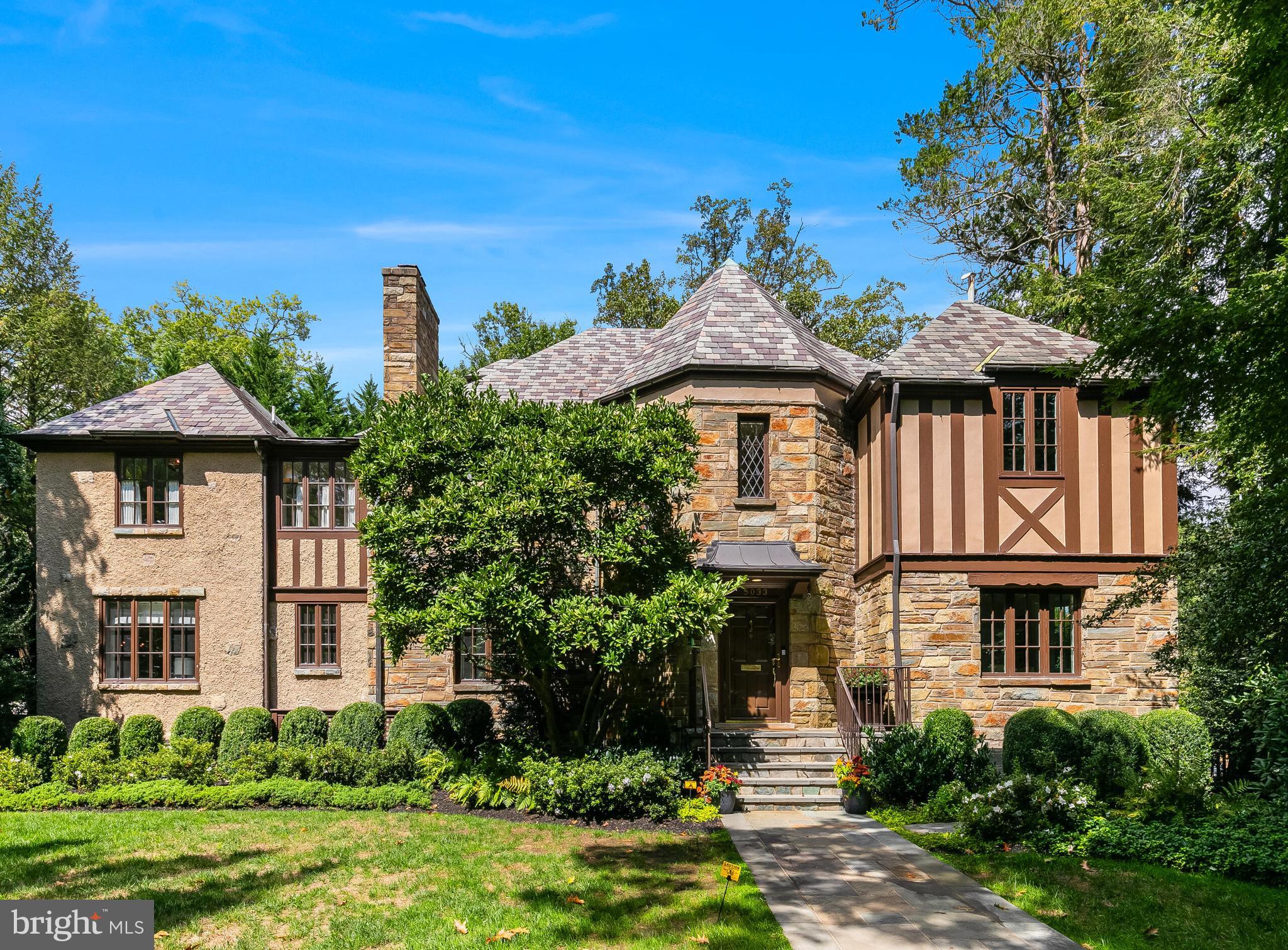 Nestled in the prestigious Spring Valley neighborhood, this 1942 Tudor Revival stands as a testament to timeless elegance, completely reimagined in 2023 to blend its historic charm with modern luxury. More than just a residence, it’s a masterpiece designed for refined living and seamless entertaining.

From the moment you approach, the home’s signature diamond-paned windows hint at its rich architectural heritage. Step inside, and you’re greeted by a stunning interplay of classic craftsmanship and contemporary sophistication, where every detail has been thoughtfully considered.

The main level exudes understated grandeur with soaring 9+ foot ceilings and sunlit spaces throughout. The formal living room, anchored by a stately wood-burning fireplace and framed by oversized windows, French doors that lead to a flagstone patio with a wood-burning fireplace, is equally suited for intimate evenings or lively gatherings. The heart of the home is the newly reimagined kitchen—crafted in 2023 by renowned architect Dale Overmyer and builder John Cecchi.  Featuring premium finishes and an effortless flow into the family and dining areas, and an outdoor patio overlooking the expansive swimming pool, this space is as functional as it is beautiful, designed to inspire connection and warmth.

The primary suite is a private retreat of unparalleled comfort. With its own wood-burning fireplace, dual walk-in and cedar closets, and a spa-like bath, it offers a haven for relaxation. The dual-sided bathroom is flooded with natural light from a skylight above the jetted soaking tub and includes private vanities, 2 separate water closets, and a steam shower.

Upstairs, five unique bedrooms provide a wealth of possibilities.  Two of the bedrooms share a bath, ideal for family living, while another features a private en suite. The Parisian-style suite, with its own full bath, offers a serene space for long-term guests, an au pair, or creative pursuits.

The lower level is a self-contained living area with its own private entrance, second kitchen, bedroom, recreation room, and two full baths. Whether it serves as an in-law suite, home gym, or creative studio, this flexible space adapts effortlessly to your lifestyle.

Step outside, and the home transforms into a private oasis. French doors open to a spacious deck with a built-in grill and serene, tree-lined views—perfect for hosting or relaxing. The professionally landscaped, fully fenced yard is a haven of tranquility, complete with irrigation, landscape lighting, and a heated pool with a remote-controlled cover. A custom stone patio with a wood-burning fireplace invites cozy evenings under the stars.

Additional highlights include a billiard room/library, built-in Sonos sound system, separate audio/visual room, dual laundry facilities, two garages, and a Ring security system—all situated on an expansive .33-acre lot.

Located in the coveted Spring Valley community, this home offers the best of both worlds: the peace of suburban living with the convenience of urban access. Enjoy weekend brunches in the Palisades, quick commutes to downtown DC or Tysons, and scenic strolls through nearby parks and trails.

This is more than a house—it’s a celebration of history and modernity, where every space tells a story of thoughtful design, timeless elegance, and a life well-lived.