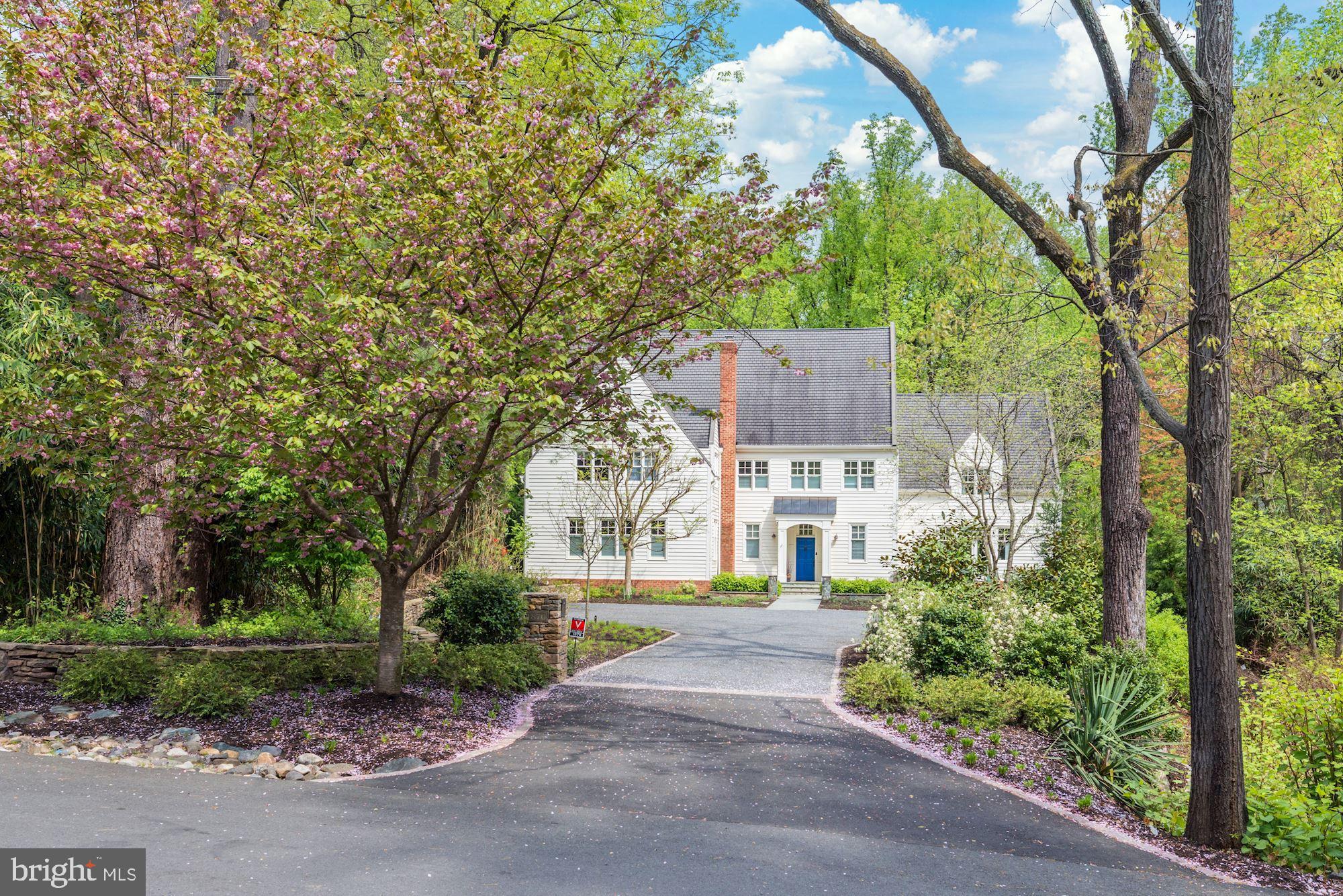 Landscaped solitude meets thoughtful design in this Franklin Park haven. Sited on a 1.11 acre lot adjacent to parkland and reminiscent of a country lane with ample parking, this elegant, modern interpretation of an English country house encompasses approximately 8,339 SF+/- of living space, including 6 bedrooms, 5 full and 2 half bathrooms. A 2019 designer kitchen with a bifolding glass wall that opens up to an incredible terrace with substantial hardscaping and landscaping that includes terraced cocktail pools with waterfalls, a bar with built-in grill, shade sails covering an outdoor lounge are, a fire pit, a bucolic, flat lower yard and private play area to complete this idyllic property.  The home’s rooms are graciously sized inviting form and function that simultaneously caters to large entertaining and comfortable cozy family living. Exquisite views pour in throughout the first level and are beautifully framed by 10’ ceilings, large windows, and the bifolding glass wall as well as multiple French doors.  Just inside the front door, a mosaic tiled entry hall with generous walk-in coat closet connects the home’s main living areas. The thoughtful layout of the rear courtyard encourages indoor/outdoor entertaining both from the expansive and bright family room with built-ins to the designer kitchen with bifolding glass wall (including a full-wall screen) that opens to the sweeping bluestone terrace with multiple lounges and outdoor seating areas. In the kitchen, modern cabinetry presides with designer tile and lighting selections, gourmet appliances including a new built-in espresso machine, and a substantial quartz island with waterfall edge and pendant lighting. Adjacent to a 2nd island is an intimate breakfast area offset by the central dual-sided masonry wood-burning fireplace. The breakfast room and kitchen windows offer views of both sides of the home’s bucolic grounds. The kitchen’s front French doors open to an expansive, fully fenced kitchen-garden with fruit and vegetable patches—truly a cultivator’s dream. The formal salon with a large bar, gracious formal dining room, living room and powder room complete the first level.  Tasteful accents like gently dormered windows bring charm to the home’s upper level, where a serene primary bedroom suite—complete with large private dressing area, sitting area with custom closet built-ins that opens to primary bath with rustic tumbled stone tile and countertops—is the perfect place to unwind.  Four bedrooms, two with renovated ensuite baths and two with individual toilets and sinks but share a bath all centrally meet. A chic laundry room with new washer and dryer and expansive hall linen closet complete the generous upper foyer. The loft level offers a sophisticated, and extremely private library with a stunning ceiling treatment, custom built-ins and designer finishes. Lastly, there is a sixth bedroom and full bath, and a bonus room leading to more unfinished storage space. The lower level adds 1,774 SF+/- of extra living space, accommodating garage access large mudroom, a mirrored home gym, incredible custom stone temperature controlled wine cellar and tasting room with slate floors, walls and tiled barrel-pointed ceiling and custom wine racking and displays. An ample recreation room and powder room round out the space. The lower garage driveway includes a lit basketball hoop and garden shed. Landscape lighting and irrigation have been recently installed, and a whole-house generator is included.   Sited beautifully in perhaps the most coveted spot in all of Franklin Park, a community known for its special combination of mature trees, charming rolling hills, and extremely convienent location which offers close proximity to the best that McLean and North Arlington have to offer, and is also ideally situated just minutes to the George Washington Parkway, 1-66, Tyson’s Corner, and the Capitol Beltway.