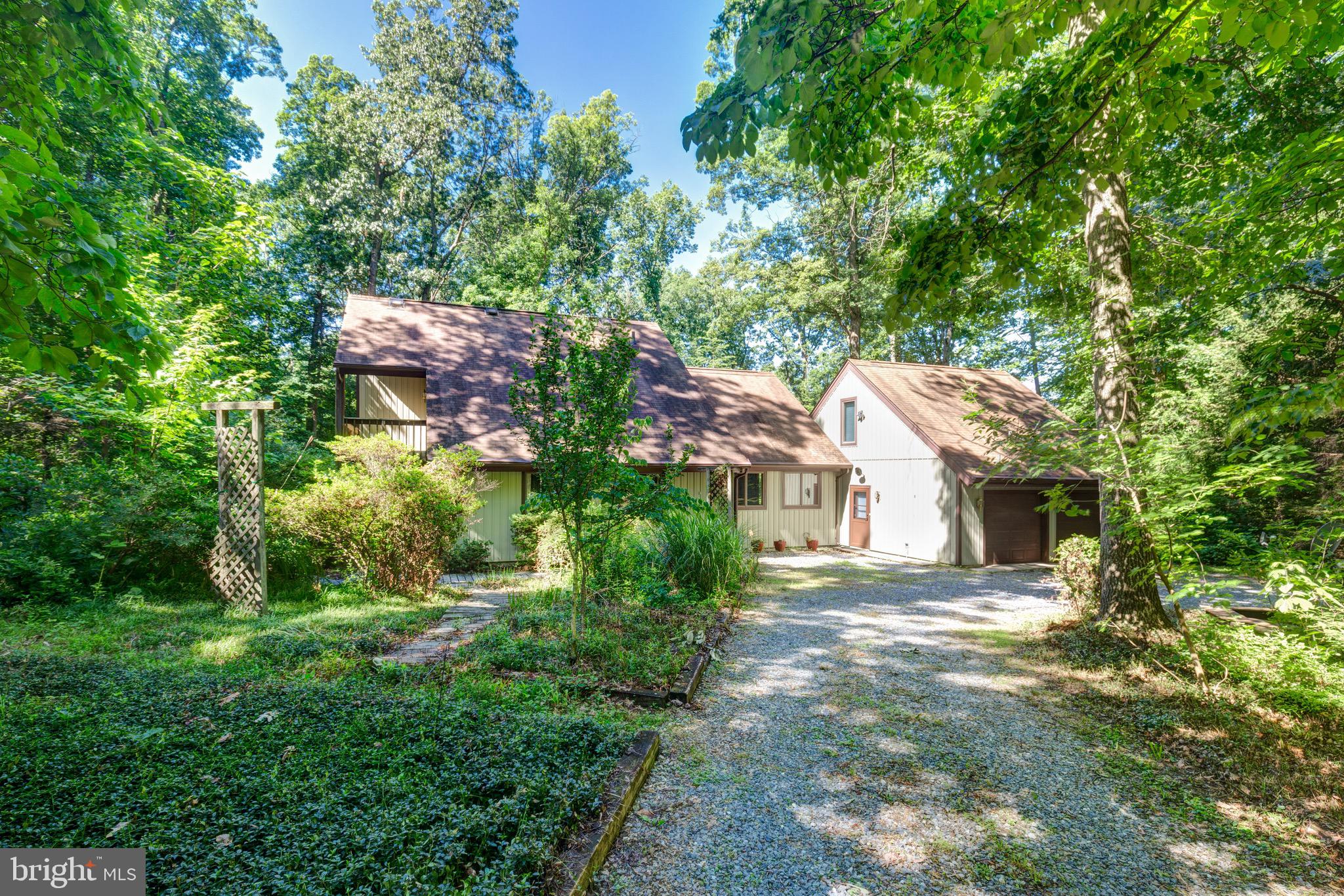Nestled among the trees on just over 5 private acres, this charming 4-bedroom, 2-bath home offers the perfect balance of peaceful seclusion and convenient access to Westminster. Surrounded by nature, the property features two  ponds, wooden walkways that meander around the home, and a true wooded retreat atmosphere.
Inside, you'll find beautiful hardwood floors throughout and an abundance of natural light from oversized windows that bring the outdoors in. The main level offers three bedrooms and a full bath, along with a spacious living room featuring vaulted ceilings and a cozy wood-burning fireplace. A separate family room provides additional space for relaxing, entertaining, or everyday living.
The lovely kitchen features open shelving, stone countertops, natural wood cabinetry, and  opens to a large  deck overlooking the natural beauty of the property—perfect for morning coffee, outdoor dining, or enjoying the peaceful surroundings.
The entire upper level is dedicated to a private primary suite retreat, complete with multiple closets, a full bath, a large skylight, and sliding glass doors leading to a private deck. An additional unfinished storage area offers potential for future expansion or additional living space.
Additional highlights include an oversized two-car garage with plenty of room for a workshop, hobby area, or extra storage; an additional storage room with chest freezer;  two  extra refrigerators; a whole house generator that conveys and established flower beds that are ready for your TLC. 
If you've been searching for a home that feels like a getaway while remaining just a short drive from shopping, dining, and amenities, this unique property is not to be missed!