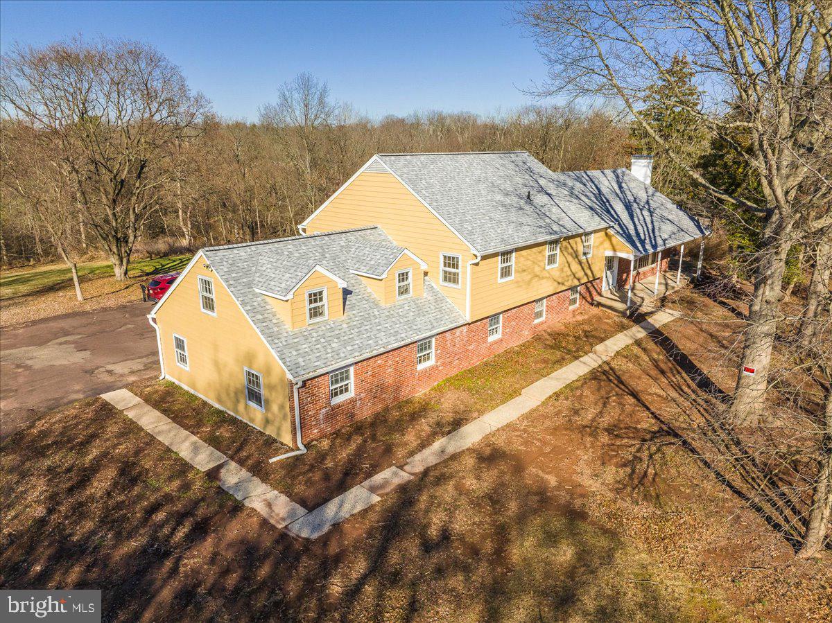Sprawling multi-level 5 Bed, 3.5 Bath home, featuring a 3-car garage! Two of the bedrooms with bath are actually two-room suites, offering private sanctuaries for larger households or guests!  This unusual home has been freshly painted and updated with meticulous attention to detail, sporting a new roof and gorgeous original hardwood flooring throughout. Sunlight pours into all rooms, even the garages. Upon arrival, you will feel the serenity of the lot as the home is set back from the street on its 1.91 acres, with your own piece of the woods in the back leading gently down to a tranquil stream below.  The living room welcomes you with oversized windows and a fireplace.  Continue to the gracious dining room, offering space for formal entertaining plus a double-door opening to a large covered-patio deck, where you'll enjoy informal outdoor parties.  The updated kitchen features sleek, natural-stone quartzite counters, tile back splash, and brand-new stainless-steel appliances.  The second floor hallway leads to a two room suite with bedroom, sitting room and bath--plus 3 more bright and airy bedrooms and a double sink full bath!  You might be tempted to use the second floor suite as your bedroom, but wait!  On the third floor, you will find another spacious two room suite with its own full bath and an unusually generous number of spacious closets, including a cedar closet.  The expansive floor at the garage level could serve as an in-law suite if you wanted a sixth bedroom, This bonus room is currently designed to serve as a spacious wet bar next to a large family room with an additional fireplace, a half- bath, a laundry room, and an inside entrance to the garage.  Plenty of closets throughout the home but if you really need to store anything else, there's an attic above the third floor that's large enough to host a square dance, and a basement that could become your shop or game room.  This home is located in the desirable North Penn School District, and is located only 5 minutes from I-476.  This one won't last.