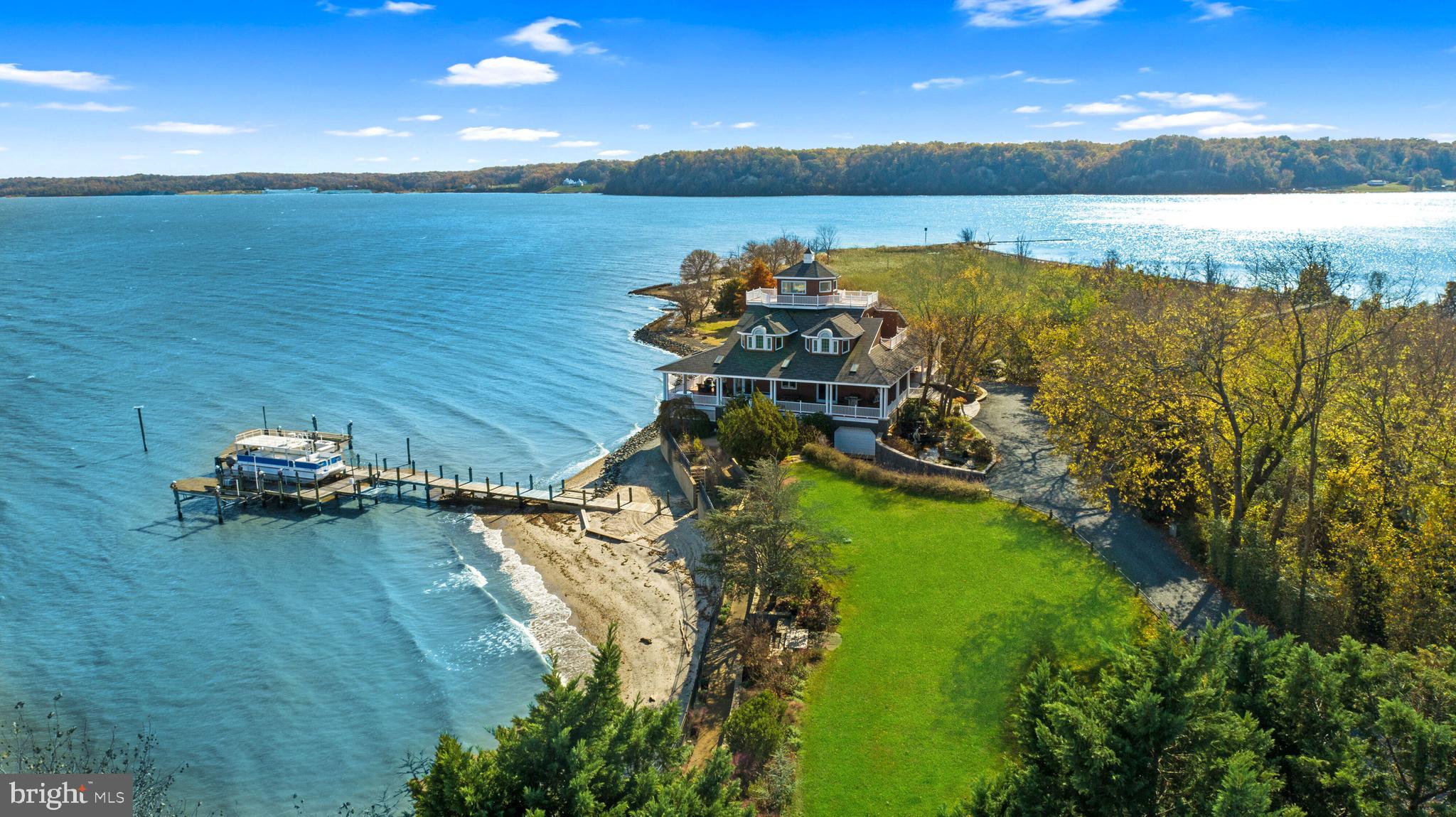 Welcome to Richlynd, the historic Pocahontas homeland on the shores of the Potomac River. This incredible property boasts an impressive 7 acre parcel, providing unrivaled privacy and serenity. Offering an unparalleled waterfront experience, the property is equipped with an expansive selection of boat docks and lifts plus a 1,300 foot pier. The home is a custom-built masterpiece, featuring over 6,800 SF of living space across 4 levels plus a sprawling 2,500 SF wrap-around covered deck designed for gracious entertaining that has space to host 150+ person seated dinner. The main level features a stunning foyer with breathtaking water views from the living room just beyond it. Both the living and dining rooms offer soaring ceiling heights and open to the wrap-around deck overlooking the water. In the spacious gourmet kitchen, you will find top-of-the-line appliances and room to seat 12 in the adjoining dinning area. A serene primary suite with covered deck access, beautiful water views, and a spa-like bath with hot tub complete the main level. Upstairs, five private bedrooms, each with their own unique water view and three full bathrooms provide ample room for all.  5-zone heating and cooling system, elevator to 3-floors, and a laundry rooms on 3-levels of the home ensure comfort and convenience. On the lower level you will find a large movie room that could double as an extra bedroom, an entire guest apartment with a bedroom, full bath, full kitchen, and living area, plus a 5-car garage and workshop. Immerse yourself in luxury with architecturally stunning details, large windows, and a floor plan that enhances the connection to the waterfront. Perfect for hosting events large and small with onsite parking for over 30 vehicles, Richlynd is the epitome of waterfront luxury – where the serene beauty of nature meets the refined elegance of a thoughtfully designed residence. Unquestionably, this property presents the rare opportunity to own a piece of waterfront paradise.
