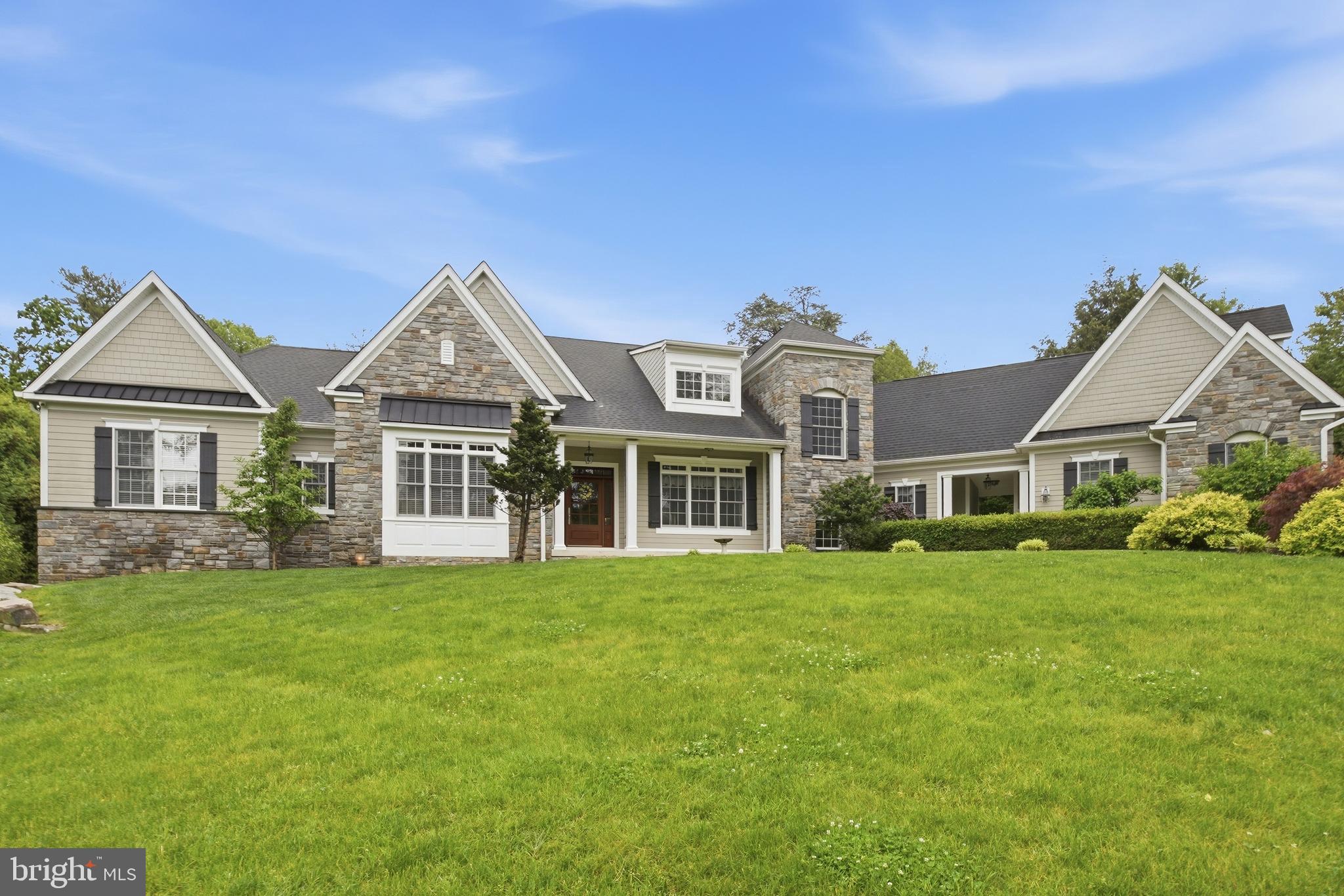 Sited on a magnificent 1.74-acre lot with mature perimeter evergreens and thoughtful plantings which offer exceptional privacy all 4 seasons and scenic views, this remarkable home is a rare find. The exterior craftsmanship displays a striking combination of Wissahickon schist stone and durable Hardie Plank siding, creating a commanding curb appeal. Custom built with no expense spared, all systems and major components are of the highest quality and only 12 years young. The property features dual walkways, with one leading to the main front porch and another guiding you to the breezeway that connects the back foyer to an oversized, attached two-car garage. Stepping onto the front porch, a custom front door with sidelights and a transom window opens into a front to back foyer featuring hardwood floors with herringbone detail. The layout offers an outstanding flow. To the right, the gourmet kitchen comes equipped with premium Wolf stainless steel appliances, including a double oven, warming drawer, six burner stove with custom tile backsplash, and a trash compactor. Recessed lighting brightens the space, complemented by cabinetry with illuminated glass fronts. A kitchen sink frames a view through a triple window. The large island provides seating for four, a prep sink, and a specialized lower baking counter with a lift up mixer cabinet. Durable tile lines the prep area, transitioning into hardwood around the island and through the adjacent breakfast room. This breakfast area includes custom cabinets. A well appointed butler's pantry connects the spaces, offering additional cabinetry, closets, and a bar sink. A double sided gas fireplace creates a warm ambiance enjoyed from the kitchen, breakfast area, and family room. On the family room side, this fireplace features a full wall of stacked stone rising to meet soaring ceilings. French doors open from the family room out to a huge patio that overlooks a spectacular yard, beautifully landscaped with sweetbay magnolias, Southern magnolias, holly trees, and 5 sugar maples. This wing is completed by a professional first floor office, a powder room, and a rear foyer leading to the breezeway. To the left of the foyer, the formal living room and dining room feature classic hardwood flooring and large windows. A nearby hallway leads to a full hall bathroom with tile flooring and a shower over tub combination, as well as a comfortable bedroom. The spacious primary bedroom suite is privately tucked away, featuring a tray ceiling, a dressing area, and a custom walk in closet. The primary bathroom offers tile flooring, a tiled stall shower, a deep soaking tub, double sink vanity, and a private water closet. This primary retreat includes its own French door opening directly to the patio. A hardwood staircase leads to the second floor, which offers endless possibilities. This level stands fully ready to be finished, can easily accommodate two to three additional bedrooms, and comes already plumbed for a full bathroom. Downstairs, the full basement features impressive 9'  ceilings and an outside exit serving as a clean canvas ready for your customization to become a recreation room, home gym, media center, or golf simulator. The location is incredible, offering privacy and convenience. The home sits just minutes from both the Meadowbrook (2 blocks) and Jenkintown train stations, providing effortless commuting options, and is close to local parks, shopping, and dining. This remarkable home includes a wealth of upgrades throughout. Book your appointment today!   **floor plan and additional photos available**