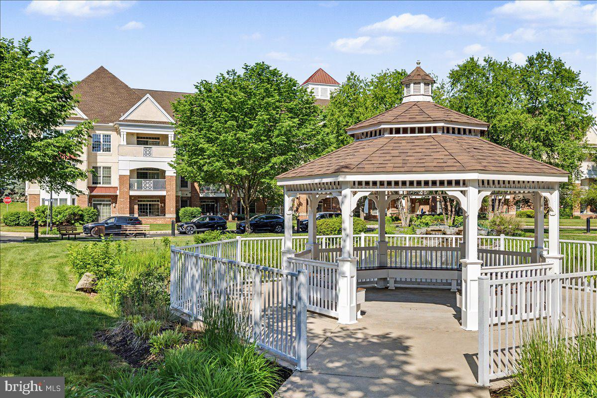 Welcome to carefree living in the highly sought-after 55+ community of Meridian Square — the perfect opportunity to downsize or right-size without sacrificing comfort, space, or storage. Ideally located within walking distance to Wegmans, Valley Square, and an impressive variety of dining and shopping destinations, this community offers both convenience and connection.
Secure entry welcomes you into a beautifully maintained building with a warm and inviting common sitting area, ideal for socializing with neighbors or enjoying a quiet change of scenery. Inside your home, rich wood flooring flows throughout the main living areas, creating a seamless transition between the living room and dining room, an ideal layout for entertaining or relaxed everyday living. The kitchen is thoughtfully designed with a two-tier granite island for meal prep, casual dining, and gathering with guests. Stainless steel appliances, gas cooking, 42-inch cabinetry, and an abundance of storage make this space as functional as it is beautiful, ideal for those who love to cook and entertain.
Sliding glass doors lead to a private covered patio, the perfect setting for morning coffee or evening conversations.  The spacious owner’s suite offers exceptional closet space, including a walk-in closet with professionally installed organizers for the clothing enthusiast, plus an additional double-door closet. The ensuite bath features neutral gray tones, tiled flooring, a relaxing soaking tub, and a separate stall shower.
A second light-filled, front-facing bedroom offers wonderful flexibility as a guest bedroom, home office, den, or additional TV room. Adjacent to the bedroom are a full hall bath and a private laundry room complete with washer and dryer.
Residents of this active adult community enjoy access to a beautifully appointed clubhouse featuring a cozy fireplace, multiple gathering spaces, billiards, ping pong, cards, arts and crafts, book clubs, and a shared library with custom built-ins. A full kitchen accommodates both private and community events, while the outdoor pool offers the perfect retreat on warm summer days.
This community truly offers the lifestyle you’ve been waiting for — low-maintenance living with abundant amenities, social opportunities, and the storage and comfort you deserve