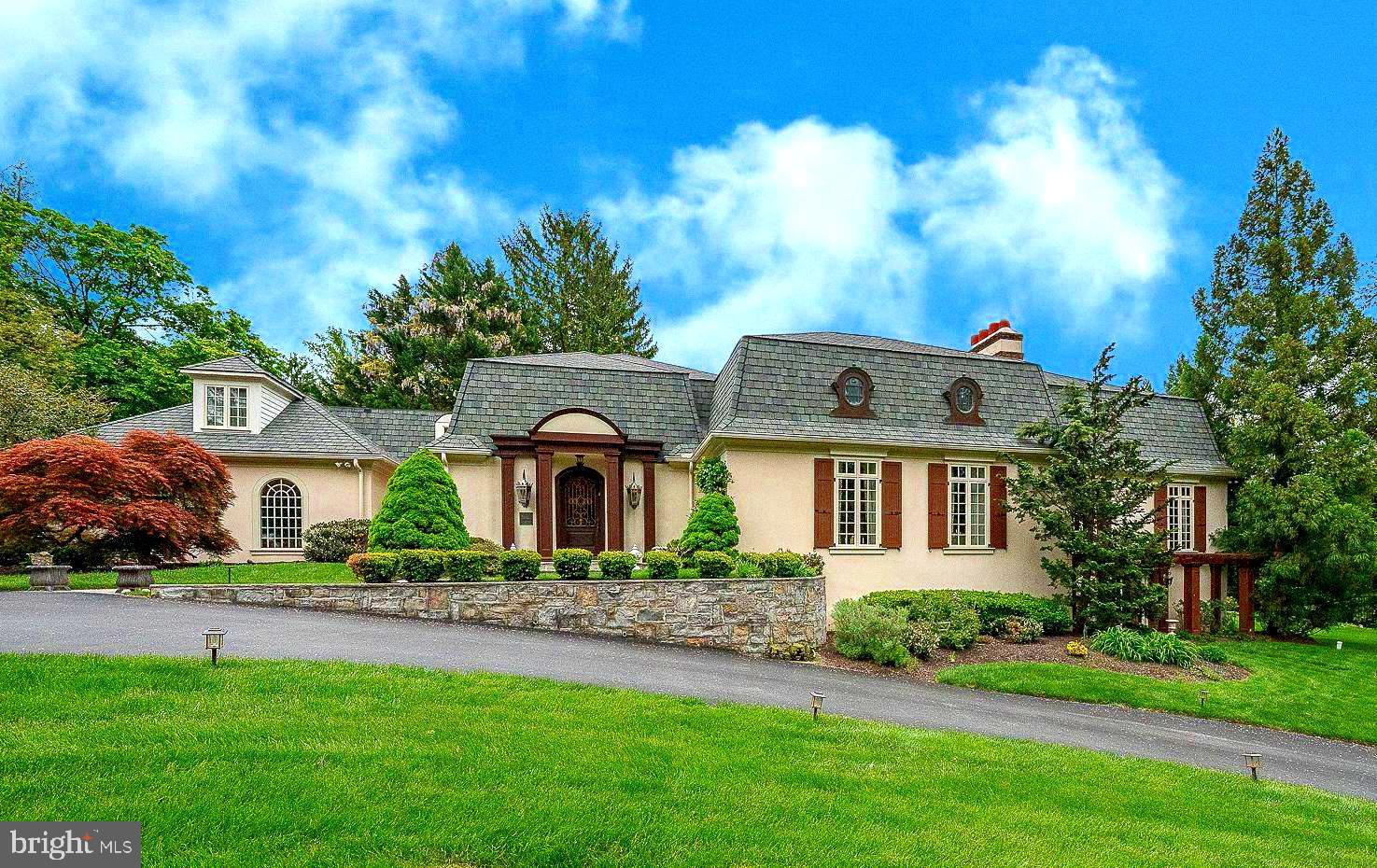 Welcome to 160 Abrahams Lane. Ideally situated along a picturesque stretch of Villanova and directly across from the renowned Ardrossan Estate, this exceptional French Colonial–inspired residence offers 5 Bedrooms and 5.1 Baths, showcasing timeless architectural character and generously scaled, light-filled living spaces. Designed around a stunning courtyard patio, the home seamlessly connects indoor and outdoor living, complemented by beautifully landscaped grounds, a built-in pool, and jacuzzi.
A dramatic two-story Foyer leads into a soaring Great Room with a gas fireplace, expansive floor-to-ceiling windows, and a graceful step-down design that enhances the sense of volume and light. This impressive space offers both comfortable Living and Formal Dining areas. A central hallway framed by multiple sets of French doors with pediments opens directly to the Courtyard, creating an elegant flow for entertaining and everyday living.
Hardwood flooring extends throughout much of the main level, adding warmth and continuity. Just off the Foyer is a Formal Powder Room and entry to the Family Room, which adjoins the expansive Kitchen and Breakfast Area. Direct access to the Courtyard Patio enhances an effortless indoor-outdoor connection.
The chef’s Gourmet Kitchen is thoughtfully designed for both function and enjoyment, featuring abundant cabinetry, a center island with granite counter-top, and a ceramic subway tile backsplash. Commercial-grade appliances include a Five Star six-burner gas cooktop with dual ovens, Viking exhaust hood, pot filler, Sub-Zero paneled refrigerator, and two Bosch dishwashers. With ample space for a full kitchen table, this inviting area is perfect for gathering, dining, and making the most of everyday living as well as entertaining. A Butler’s Pantry with wet bar and wine refrigerator connects seamlessly to a functional Mudroom offering access to the attached Two-Car Garage with a bonus storage room, as well as a side yard entry. A paver pathway extends from this area through the side yard, leading to the pool and outdoor living spaces.
At the opposite end of the central hallway, the Library offers a refined retreat with a gas fireplace, floor-to-ceiling windows, and walls of custom built-in bookshelves. The privately situated main floor Primary Suite features multiple custom-fitted closets and a spa-inspired Bath with dual vanities, soaking tub, seamless glass shower, and private water closet. Generous natural light filters through large windows throughout the suite.
The second level offers four well-proportioned Bedrooms, including two with ensuite Bathrooms. The remaining Bedrooms share a Hall Bath, with one currently serving as a Home Office and Sitting Room. A second-floor Laundry Room and walk-in attic provide added convenience and storage.
The finished lower level expands the living space with a large recreation area featuring a gas fireplace and French doors to the exterior, a wet bar, Full Bath, and additional rooms ideal for office, study, or fitness use. With its flexible layout and private access, this level is also well-suited for use as an in-law or au pair suite. A large unfinished utility area provides extensive storage.
Distinctive details such as deep-silled windows, high ceilings, custom millwork, and elegant brass hardware reflect the home’s craftsmanship and character throughout. A whole-house backup generator provides added comfort, peace of mind, and everyday convenience. A true highlight of the property is the expansive courtyard setting, complemented by a pool and jacuzzi, creating a private and picturesque outdoor retreat.
Ideally located just minutes from downtown Wayne, this home offers easy access to boutique shopping, dining, SEPTA Regional Rail, and major roadways, combining Main Line charm with everyday convenience.
Serviced by the award-winning Radnor School District, and near renowned private schools: Episcopal Academy, Agnes Irwin, and the Haverford School.