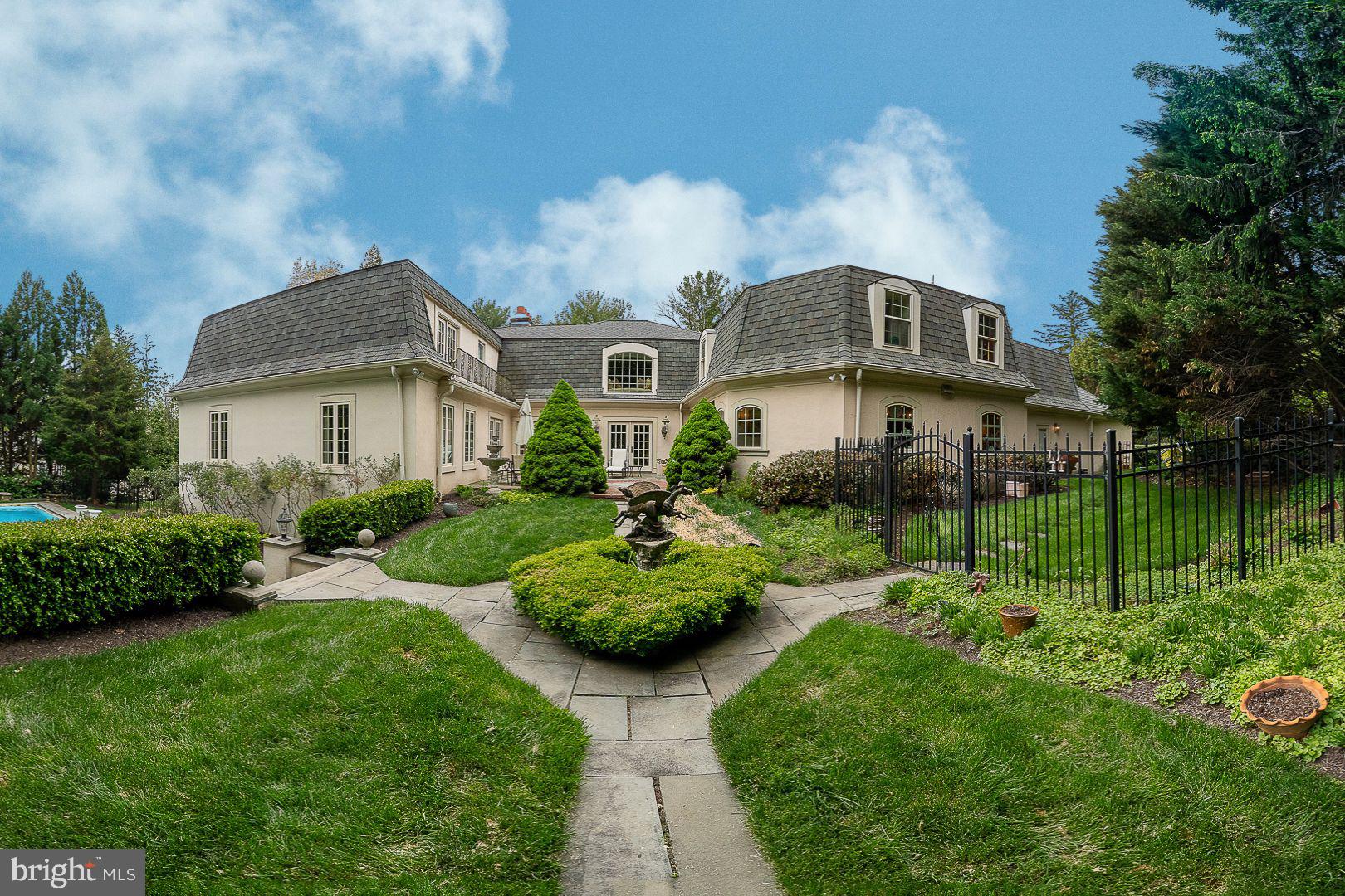 Welcome to 160 Abrahams Lane. Ideally situated along a picturesque stretch of Villanova and directly across from the renowned Ardrossan Estate, this exceptional French Colonial–inspired residence offers 5 Bedrooms and 5.1 Baths, showcasing timeless architectural character and generously scaled, light-filled living spaces. Designed around a stunning courtyard patio, the home seamlessly connects indoor and outdoor living, complemented by beautifully landscaped grounds, a built-in pool, and jacuzzi.
A dramatic two-story Foyer leads into a soaring Great Room with a gas fireplace, expansive floor-to-ceiling windows, and a graceful step-down design that enhances the sense of volume and light. This impressive space offers both comfortable Living and Formal Dining areas. A central hallway framed by multiple sets of French doors with pediments opens directly to the Courtyard, creating an elegant flow for entertaining and everyday living.
Hardwood flooring extends throughout much of the main level, adding warmth and continuity. Just off the Foyer is a Formal Powder Room and entry to the Family Room, which adjoins the expansive Kitchen and Breakfast Area. Direct access to the Courtyard Patio enhances an effortless indoor-outdoor connection.
The chef’s Gourmet Kitchen is thoughtfully designed for both function and enjoyment, featuring abundant cabinetry, a center island with granite counter-top, and a ceramic subway tile backsplash. Commercial-grade appliances include a Five Star six-burner gas cooktop with dual ovens, Viking exhaust hood, pot filler, Sub-Zero paneled refrigerator, and two Bosch dishwashers. With ample space for a full kitchen table, this inviting area is perfect for gathering, dining, and making the most of everyday living as well as entertaining. A Butler’s Pantry with wet bar and wine refrigerator connects seamlessly to a functional Mudroom offering access to the attached Two-Car Garage with a bonus storage room, as well as a side yard entry. A paver pathway extends from this area through the side yard, leading to the pool and outdoor living spaces.
At the opposite end of the central hallway, the Library offers a refined retreat with a gas fireplace, floor-to-ceiling windows, and walls of custom built-in bookshelves. The privately situated main floor Primary Suite features multiple custom-fitted closets and a spa-inspired Bath with dual vanities, soaking tub, seamless glass shower, and private water closet. Generous natural light filters through large windows throughout the suite.
The second level offers four well-proportioned Bedrooms, including two with ensuite Bathrooms. The remaining Bedrooms share a Hall Bath, with one currently serving as a Home Office and Sitting Room. A second-floor Laundry Room and walk-in attic provide added convenience and storage.
The finished lower level expands the living space with a large recreation area featuring a gas fireplace and French doors to the exterior, a wet bar, Full Bath, and additional rooms ideal for office, study, or fitness use. With its flexible layout and private access, this level is also well-suited for use as an in-law or au pair suite. A large unfinished utility area provides extensive storage.
Distinctive details such as deep-silled windows, high ceilings, custom millwork, and elegant brass hardware reflect the home’s craftsmanship and character throughout. A whole-house backup generator provides added comfort, peace of mind, and everyday convenience. A true highlight of the property is the expansive courtyard setting, complemented by a pool and jacuzzi, creating a private and picturesque outdoor retreat.
Ideally located just minutes from downtown Wayne, this home offers easy access to boutique shopping, dining, SEPTA Regional Rail, and major roadways, combining Main Line charm with everyday convenience.
Serviced by the award-winning Radnor School District, and near renowned private schools: Episcopal Academy, Agnes Irwin, and the Haverford School.