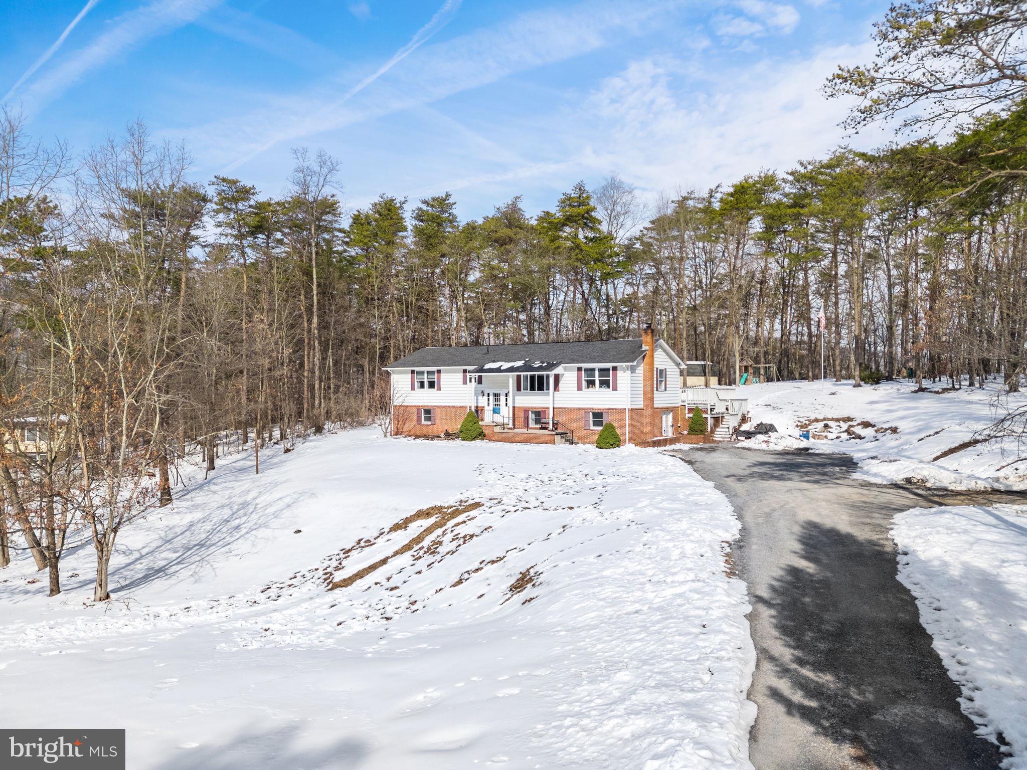 This split-foyer single-family home offers a traditional layout, generous living space, and a peaceful setting just outside Berkeley Springs. Situated on 1.61 acres and backing to trees and a utility right-of-way, the property provides long-term rear privacy with no future homes planned behind it.

The home features 4 bedrooms, 3 full baths, and approximately 2,612 square feet of finished living space, including a fully finished walk-out lower level. Interior highlights include hardwood floors, partial carpeting, a formal dining room with French doors, and a comfortable living room with an electric fireplace. The eat-in kitchen offers an island and convenient access to outdoor living areas.

Outdoor spaces include a large deck with pergola and a screened porch, overlooking a spacious yard that backs to trees. The property also includes a 10x20 storage shed and a fenced dog run area, providing flexibility for storage, pets, and outdoor use.

Recent updates and system details include architectural shingles installed approximately four years ago, hot water heater replaced in 2023, a water pressure tank installed in 2016, a water softener, and a recently pumped septic system. The home is equipped with two heating and cooling units with separate thermostats, offering efficient comfort on both levels.

Located in a quiet, private setting while remaining convenient to town and major commuter routes, this property offers a rare combination of space, functionality, and accessibility.