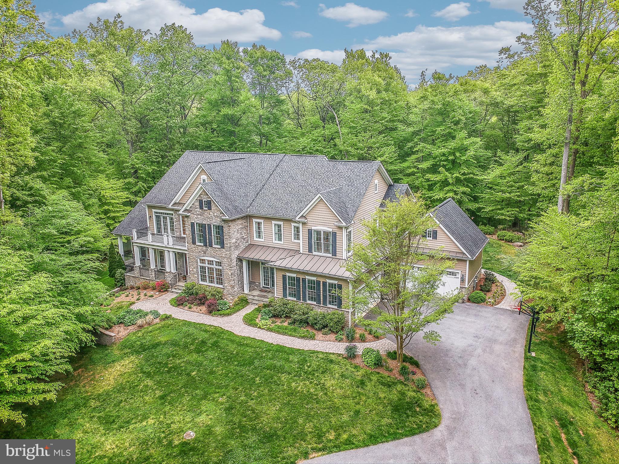 Elegant, custom built home that sits in a very private, park like setting. Just minutes from Route 50 for easy commutes.   From the moment you walk into the home you can see the attention to detail. From the 10 foot ceilings to box moldings to the Brazilian Cherry hardwood flooring, this home has it all.  The large gourmet kitchen with custom cabinets, 6 burner propane stove, warming drawer and extra large island opens to a large family room with coffered ceilings and a wall of windows that brings an abundance of natural light. The never-ending wooded views are brilliant.  The entire home is incredibly gorgeous. The morning room off the kitchen is the perfect place to grab a cup of coffee or head out to your amazing  Azek deck; or onto the stone patio with fire pit. Curl up with a book in the sunroom that has barreled ceilings and views of the woods.  You won't mind working from home in this beautiful first floor office, with floor to ceiling windows and doors that open to the deck and backyard. There is a second small office or kids study with 3 built in cubicles off a mudroom. Relax in your own wing of the house. The second floor master bedroom with its  own wall of windows, large sitting room and spa like master bath with 6 head shower and jetted tub takes up one side of the home. You also have a balcony off the master sitting room. Across the house from the master are three bedrooms, all with their own full baths. For extra convenience, the laundry room is also on this floor. The basement has more than 3000 square feet with a large, open, living space, doors to the backyard,  roughed-in for a future wet bar area and fireplace. Just to add more to your living experience, you may never want to leave the theater room with 120-inch screen, surround sound and tiered seating. The basement also has one bedroom and a full bath along with a craft room and storage. This home has so many custom features that you have to see it for yourself. There are two, 2-car garages with 12 foot ceilings. Led lighting is throughout the home. The exterior has three flagstone porches, exterior audio system, and professional lighting on the exterior. All set in a small community of 6 estate homes on an average of 5 acre lots. You don't want to miss this one of a kind custom home.  It is truly amazing!