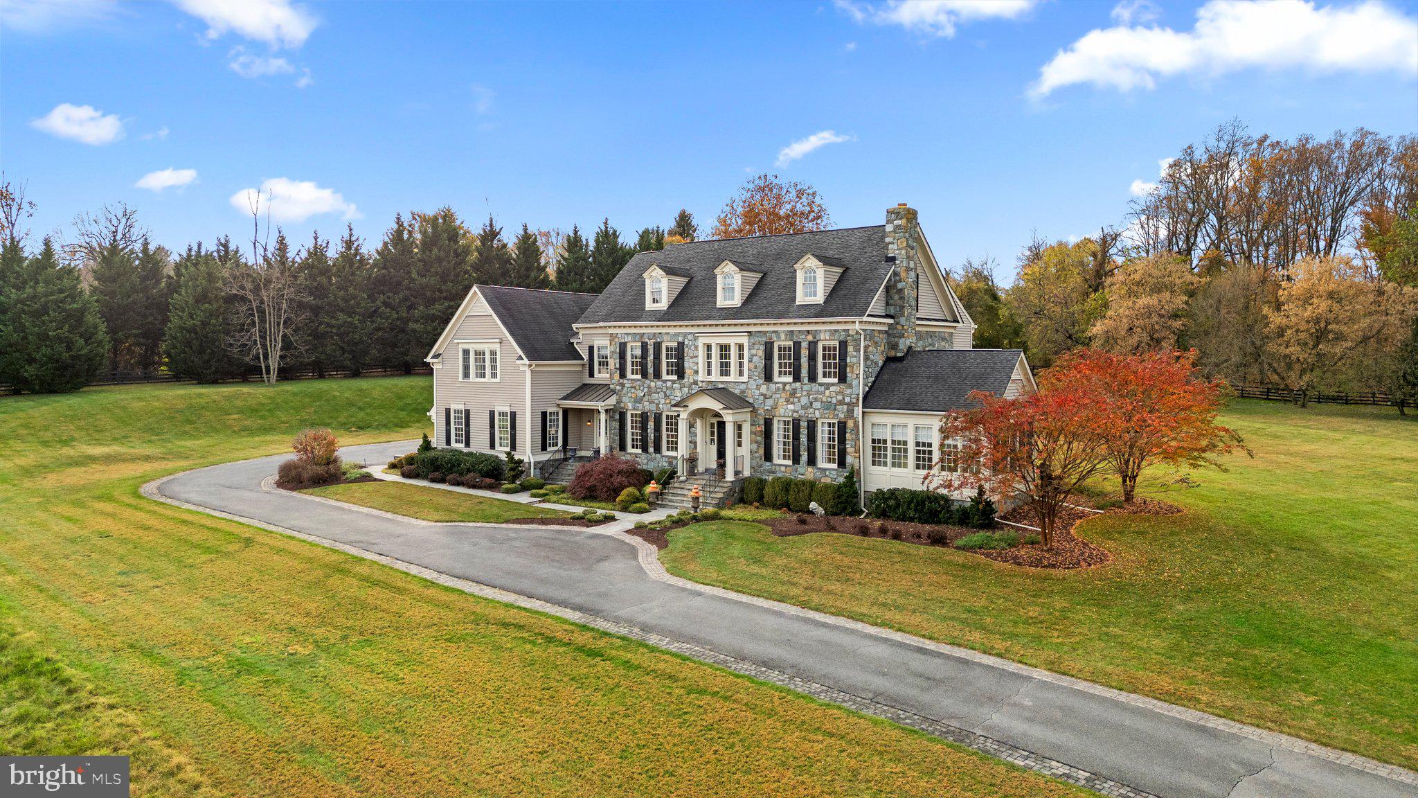 Welcome to a Dream Estate of Unparalleled Elegance and Serenity. Nestled on over 10 acres of breathtaking beauty in the prestigious Bancroft community of Sandy Spring, 17400 Ashton Green invites you to a life of luxury, sophistication, and tranquility. Positioned high on the property, this estate captures panoramic views of rolling landscapes and conservation areas from nearly every room, making it a rare treasure in this exclusive enclave of only 44 homes. The Eagles Nest, Mitchell and Best's largest model is designed to suit those who desire refined retreat-style living or the ultimate equestrian property. This extraordinary five-bedroom, five-and-a two-half-bath sanctuary spans over 9,000 square feet across four finished levels, displaying unparalleled  craftsmanship in every detail. Stepping into the grand two-story foyer, you are immediately captivated by the exquisite detailing: from designer accent moldings to lustrous hardwood floors. An elegant, curved staircase sets a regal tone for the residence. Just beyond, double French doors open to a private home office, perfect for refined work-from-home days. The main level offers an abundance of spaces for both intimate gatherings and grand entertaining. The cozy living room, complete with a wood-burning fireplace, flows seamlessly into the formal dining room, while a sunlit, serene sunroom offers an ideal spot to enjoy nature views or relax with a favorite book. The gourmet kitchen is a chef’s paradise, designed with inspiration in mind. Equipped with top-of-the-line appliances, a central island with breakfast bar, custom backsplash, double wall ovens, and a six-burner gas range, it’s a space where culinary dreams come alive.  This space opens to the family room, where  wall-to-wall windows with built-in benches, a tray ceiling, and a cozy stone surround gas fireplace, invite warmth and sunlight, igniting the imagination with stunning views of the estate's vast landscapes. A private rear staircase ascends to the first upper level, where you’ll find the opulent owner’s suite with its tray ceiling, step-down sitting room, two walk-in closets, and a private balcony--a tranquil retreat with commanding views. The luxurious ensuite bath  features a jetted tub, dual vanities, an oversized shower, and elegant tile flooring. Three additional bedrooms, including one with a private bath and two sharing a buddy bath, complete this level along with an open loft area, ideal for play or relaxation. The second upper level offers a fifth bedroom, another full bath, and a versatile open space that can serve as a craft room, additional office, or gathering area. The fully finished lower level extends the luxury living experience, featuring a recreation room with a stunning custom bar, game area, media room, exercise room, and a full bath. Walk-out stairs lead to a private backyard oasis, with lush landscaping carefully maintained by the HOA. The Bancroft community provides a peaceful setting with miles of walking paths, sidewalks, and a central neighborhood park with a tot lot. Don’t miss this rare opportunity to own a one-of-a-kind estate, impeccably maintained by its original owners and crafted with thoughtful detail throughout. This property stands as a testament to luxurious living, offering a retreat-like ambiance and a view that truly captivates.