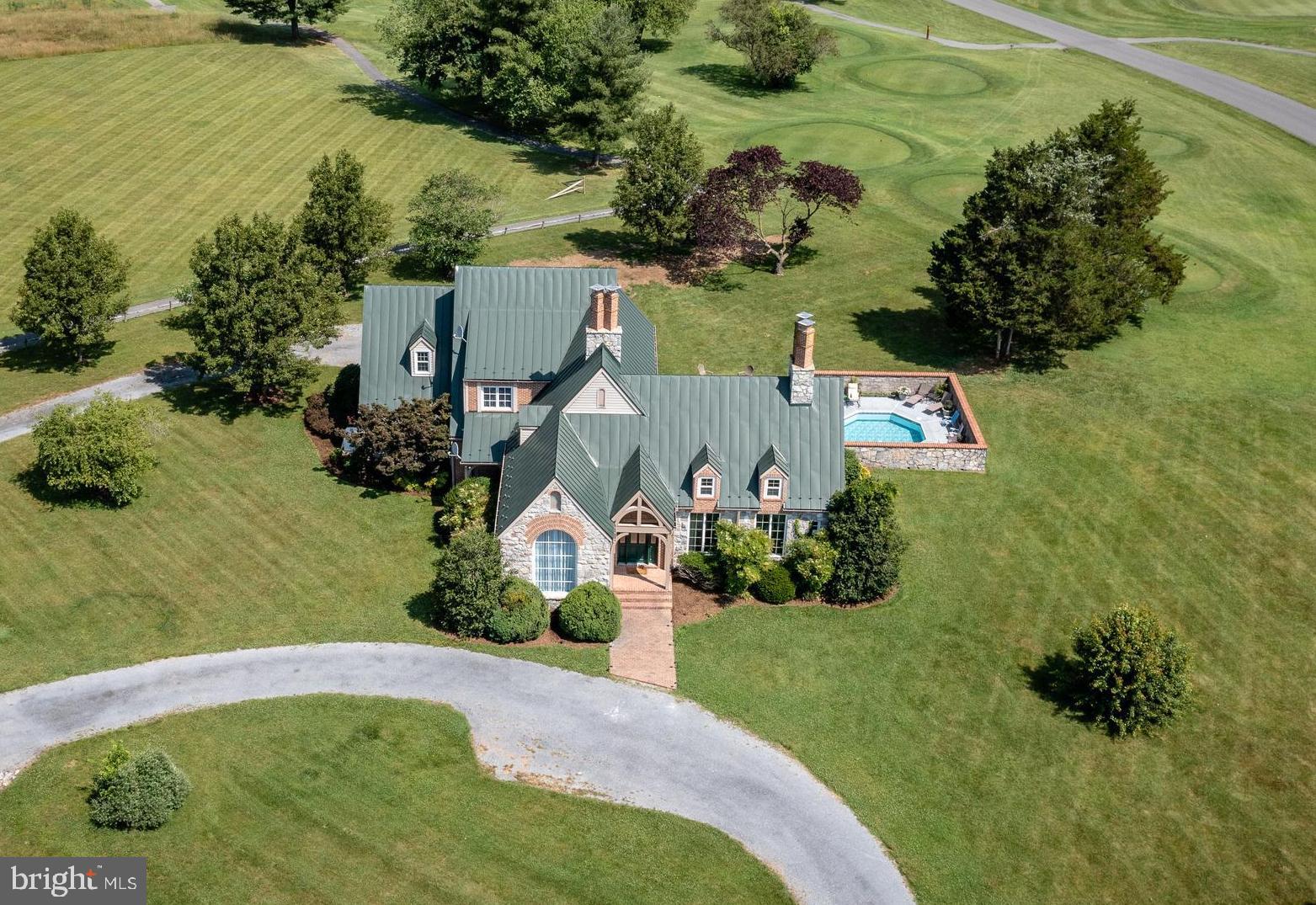 Welcome to the Stone House in Luray – A Mountain Retreat with Unmatched Views and a Pool! Please have your agent check Bright MLS agent remarks, and documents for features and income figures.  

Nestled on the 17th hole of the Caverns Country Club, this distinctive English Manor-style home with a gorgeous metal roof offers breathtaking views of the Blue Ridge Mountains to the east and the Massanutten Mountains to the west. Set on an impressive 1-acre lot, this Shenandoah Valley property provides ultimate comfort.  

As you step inside, you're greeted by an open foyer, soaring ceilings, and beautiful hardwood floors throughout the main level, setting the tone for the home’s thoughtful design. The formal dining room features a vaulted 12' ceiling with exposed beams and an elegant arched window, comfortably seating ten—ideal for hosting memorable gatherings. The expansive living room boasts a grand stone fireplace reaching almost 20' and large windows with glass double doors that allow natural light to fill the space and lead to the covered veranda, where you can take in the stunning views.

Conveniently tucked away, you'll find a den, playroom, or small resting room large enough for a single bed—an ideal flex space. Opposite this room is a recently updated full bathroom.

The heart of the home is the open farmhouse kitchen with exposed beams, equipped with a full suite of stainless steel appliances, including a double oven, granite countertops, ample cabinet space, and island seating. Just off the kitchen, a cozy eating area sits in front of a second gas fireplace and leads into a large walk-through pantry and an additional closet pantry, providing convenient access to the formal dining room. A second half-bathroom on this level and a laundry/mudroom are located nearby, with access to the three-car garage.

Upstairs, you’ll find three spacious bedrooms and a den, ideal for relaxation or additional living space. The primary bedroom is a true retreat, offering mountain views and an en-suite bathroom with a double vanity and a linen closet. The second upstairs bathroom serves the additional bedrooms and has been thoughtfully updated with new flooring, a double vanity, and a bathtub.

The lower level features a versatile living area that can be tailored to your needs, whether for recreation or extra living space.

The outdoor spaces of this home are equally spectacular. Enjoy breathtaking sunrises and sunsets while relaxing by the pool, surrounded by a gorgeous stone wall that matches the house. Make memories spending time with loved ones, grilling a meal, or gathering around the fire pit.

Additional features include high-speed internet access through Comcast/Xfinity and a whole-house generator for peace of mind. Dual HVAC systems and many windows were recently replaced. Request a list of recent improvements from your agent.

Located just minutes from historic downtown Luray, you'll have easy access to the renowned Luray Caverns, the scenic Shenandoah River, and the expansive Shenandoah National Park. An array of wineries, breweries, and restaurants are just a short drive away. Whether you're looking to unwind in nature or enjoy some family fun, the Stone House offers everything you need for an unforgettable stay.