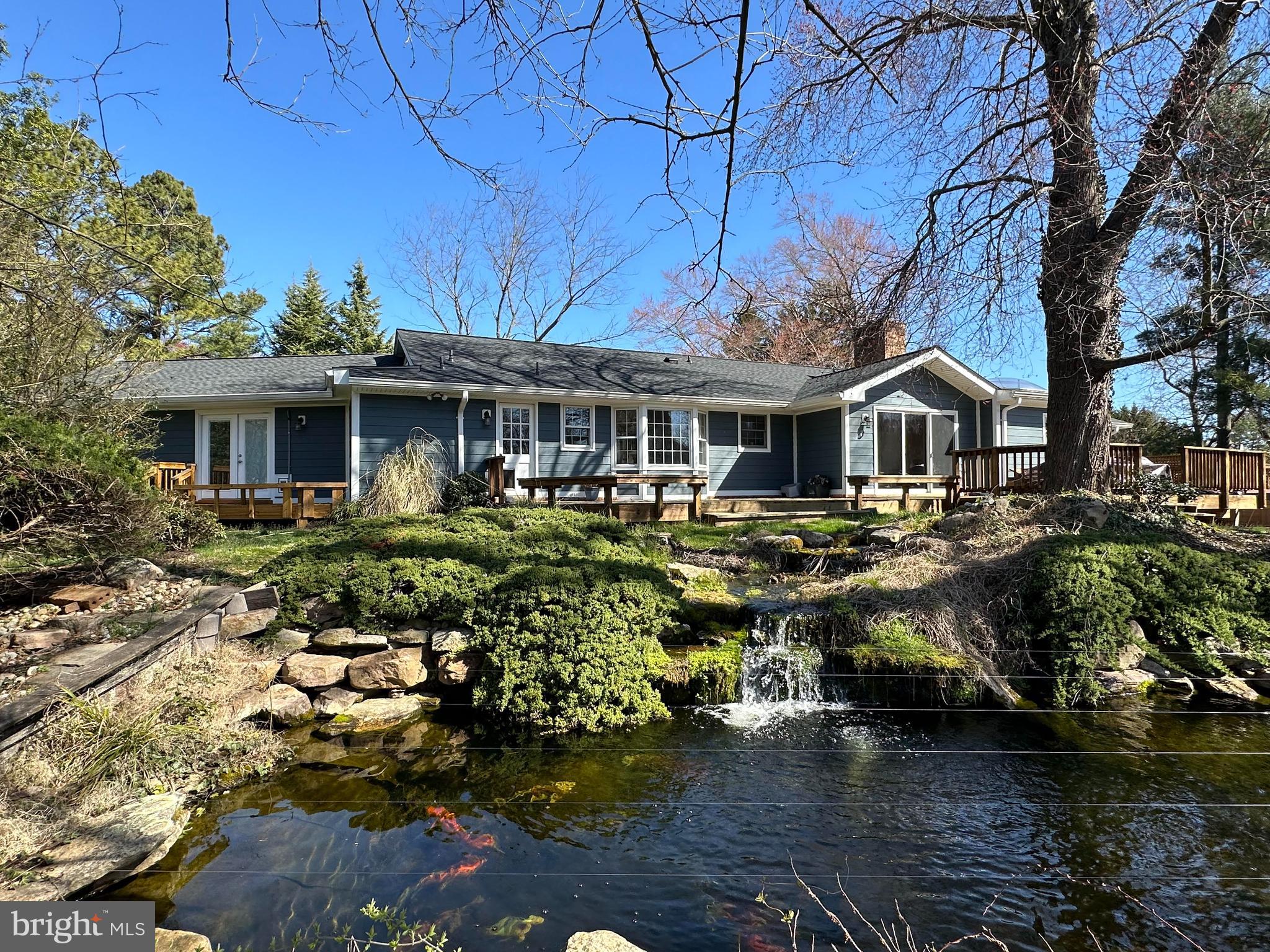 Picture yourself immersed in the serene ambiance of this rolling three-acre farm in Vienna. Just a brief ten-minute drive from downtown Vienna, Tysons Corner, and the Vienna Metro, yet worlds away in terms of tranquility and natural beauty. Nestled within the highly coveted Hunters Valley neighborhood, this property offers a blend of convenience and pastoral charm unlike any other.  This 4BR, 4.5BA home boasts over 4,000 square feet of finished space including an over 500 square foot In-Law Suite with a separate entrance.  This is one level living at its finest with two walk outs to the extensive outdoor deck and path around the pond.  Adjacent to the deck is access to a hot tub / swim spa.  The lower level is an additional finished space with a wet bar for entertaining and a full bath.  Walk out on this level to the yard and access to the deck.  The lot is extremely private and at the end of a pipestem.  The three acres also has a four stall horse barn with a large walk-in loft for storage.  A private lighted dressage ring is on the property for the horse enthusiast. When all this comes together, imagine starting your day with the gentle sounds of a cascading waterfall, as it flows into a picturesque Koi Pond, setting the perfect backdrop for your morning routine or evening relaxation. The lush pastures surrounding the property provide a sense of space and serenity, inviting you to explore and unwind in nature's embrace.
Whether you're seeking a peaceful retreat from the city's hustle and bustle or a place to cultivate your own equestrian pursuits, this farm offers an ideal sanctuary. With its prime location and captivating scenery, it's easy to see why Hunters Valley, surrounded by miles of trails and adjacent to the Cross County Trail, is a sought-after destination for those looking to experience the best of both worlds.