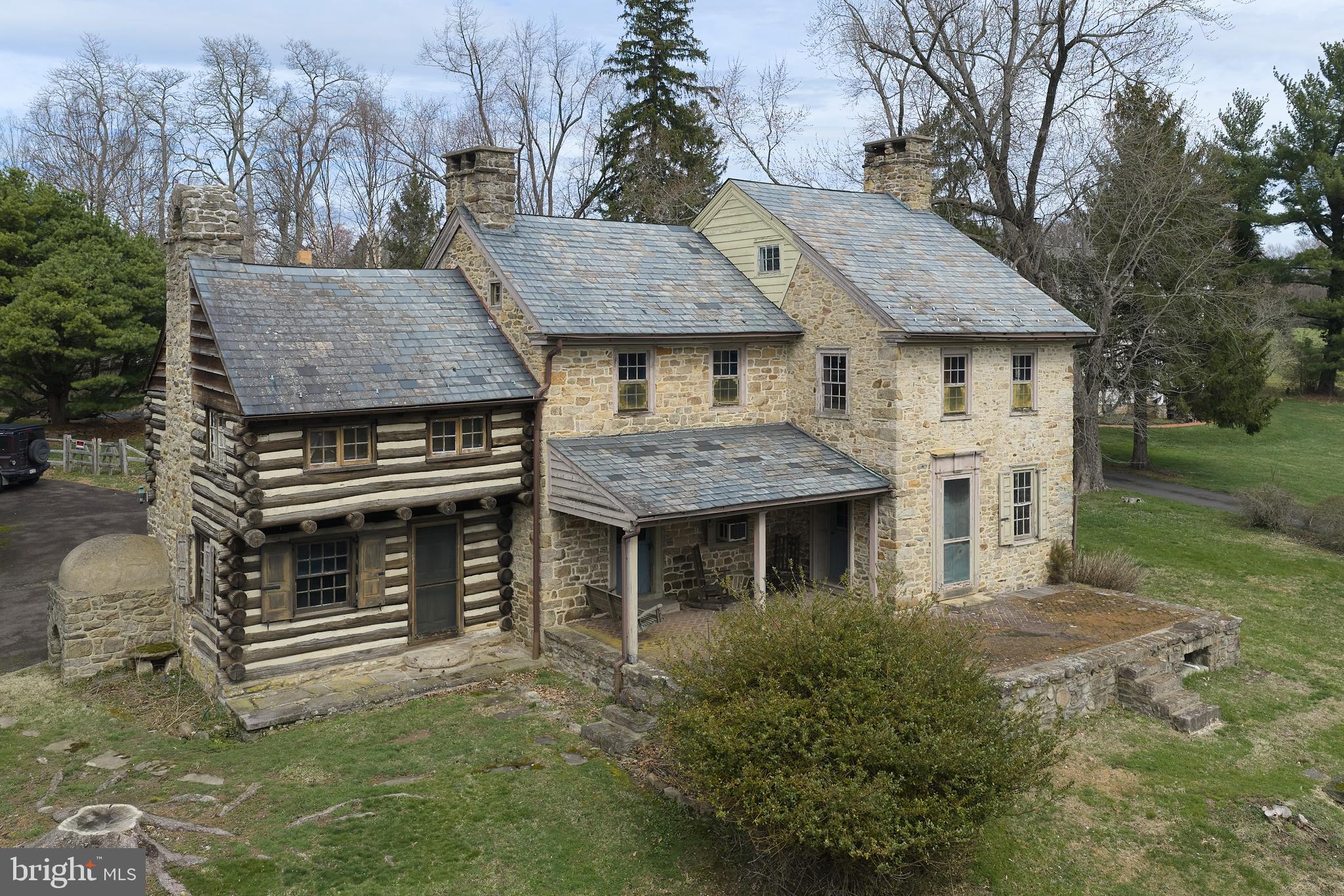 Opportunity and Potential: Own a piece of American History in the heart of Bucks County. This c.1760 stone farmhouse offers incredible potential for the right buyer. This one-of-a-kind residence is a rare fusion of an original log settler’s cabin and a handcrafted stone home, standing exactly as early colonials intended: first the cabin, then the stone additions—preserving a story that has endured for over 260 years. Whether you choose to conserve its current character, bring it back to its full historic glory, or thoughtfully update certain elements, the level of restoration is entirely up to your vision. Properties like this provide a rare chance to create a true legacy estate while adding value through customization. Inside you’ll discover:
- 4 fireplaces on the main level, each adding warmth and historic charm
- 1 additional fireplace in an upstairs bedroom currently covered but with potential to be reopened and restored
- A rare beehive oven, a true historical gem
- Original German hardware: door hinges, locks, and fittings
- Authentic window frames, doors, and craftsmanship that reflect 18th and 19th century construction
- Every room has an exterior door, six in all; the dining room has two!
Every detail tells a story. Every room transports you. 
Huge double doors lead from the dining room to the kitchen, creating a grand statement. In the living room a straight staircase leads up to the second floor, then continues to the attic—a rare feature in a vintage home. The high ceilinged attic makes the third floor a good candidate for a bedroom. A second back staircase runs from the bedroom in the log section to a mudroom downstairs, opening off the driveway. Outside, a large in-ground concrete pool and outdoor grill provide a perfect setting for entertaining, with the yard fenced for your animals. Most surprising is the stunning two-story stone watertower in the rear corner, hosting the well and pressure tank. A detached two-car garage/barn completes the country setting. The garage second floor is filled with light, perfect for a studio. You have an expansive view of the picturesque preserved farm across the road, providing serene, pastoral scenery, increasingly rare to find. You’re just minutes away from Peddler’s Village with its great shopping and dining experiences and ten minutes from New Hope. The seller is attaching an architectural proposal for a full restoration of the house, as well as a Home Inspection report. Property is being sold “as-is”.