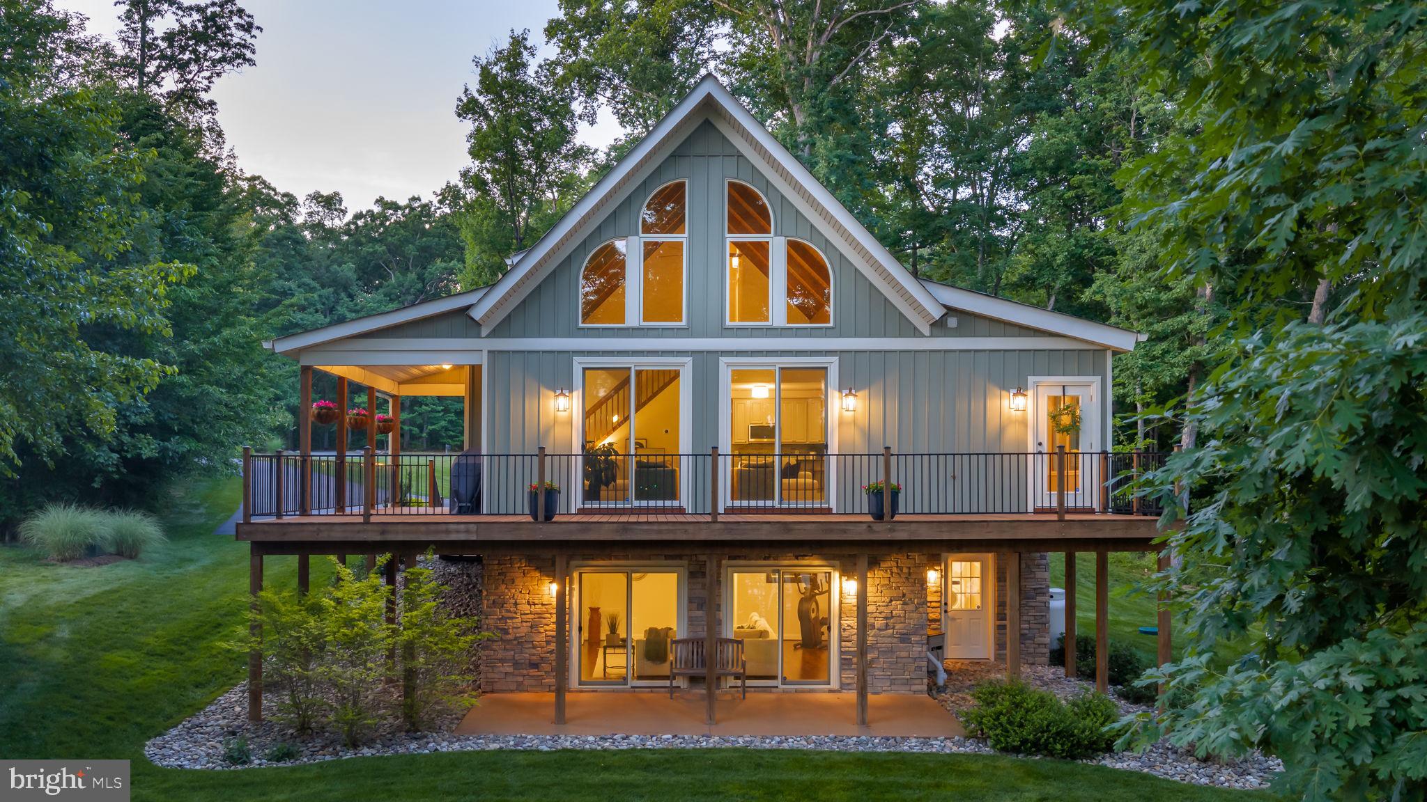 Lake Anna lake life doesn't get much better than this! Tucked away in a private cove on the public side of the lake in the highly sought-after Pleasure Island community, this beautifully remodeled Spartan-built chalet comes furnished and offers the perfect combination of stunning views, easy waterfront living, and endless fun on and off the water. Located south of the Route 208 bridge and situated on over an acre with approximately 200 feet of rip-rapped shoreline, you'll enjoy wide-water views, a gentle walk to the lake with no stairs, and your own sandy beach complete with a fire pit. Nature lovers will appreciate watching bald eagles and black hawks soar overhead and perch in the trees on the property, adding to the peaceful waterfront setting. Designed for making memories, this turn-key furnished waterfront retreat comfortably sleeps 10+ guests and is ready for immediate enjoyment. The open-concept main level welcomes you with soaring wood-beam ceilings, a wall of windows showcasing the lake, a floor-to-ceiling stone gas fireplace, a spacious dining area, sunroom, powder room, and an updated kitchen featuring granite countertops, tile backsplash, and new LG stainless steel appliances. The main-level primary suite offers a walk-in closet, soaking tub, and separate tile shower. Upstairs, you'll find two additional bedrooms and a full bath, while the finished walkout lower level is built for fun with a spacious recreation room, living area, an additional bedroom, and a full bath. Step outside and embrace the Lake Anna lifestyle. The expansive wraparound porch, oversized lakeside deck, and full-length concrete patio provide plenty of space for entertaining family and friends. Down at the water's edge, the impressive boathouse is ready for summer with two covered boat slips, both equipped with lifts, two floating jet ski pads, a bar window, refrigerator, storage area, and a sun deck perfect for relaxing after a day on the lake. Adding even more flexibility, the oversized detached two-car garage features a 24' x 28' finished, climate-controlled bonus room above with heating and air, making it ideal as a guest suite, game room, home office, gym, or bunk room. The current owners have invested extensively in upgrades, including new board-and-batten insulated siding on the home, garage, and boathouse; oversized gutters and downspouts; a new paved driveway; professional landscaping; Delaware river rock accents; an updated staircase; new carpet; fresh paint throughout all three levels; a new powder room and rear entrance; updated lighting and ceiling fans; new smoke alarms, bathroom exhaust fans, and kitchen disposal; an ADT security system; a whole-house water filtration and UV purification system; a rebuilt Carrier heat pump; rebuilt boat lifts; and much more. Additional features include Xfinity Comcast high-speed internet and cable TV, a 9-zone lake-fed irrigation system, and an invisible pet fence that surrounds the entire property, providing peace of mind for both pets and owners. This retreat is truly move-in ready and perfectly positioned in a prime central Lake Anna location, just minutes by boat from waterfront restaurants, marinas, mini golf, ice cream, and local favorites. To make this opportunity even sweeter, the Sea Ray boat and two Kawasaki three-person jet skis may be purchased separately, allowing you to start enjoying lake life from day one. Just bring your friends and family and start making memories at the lake.