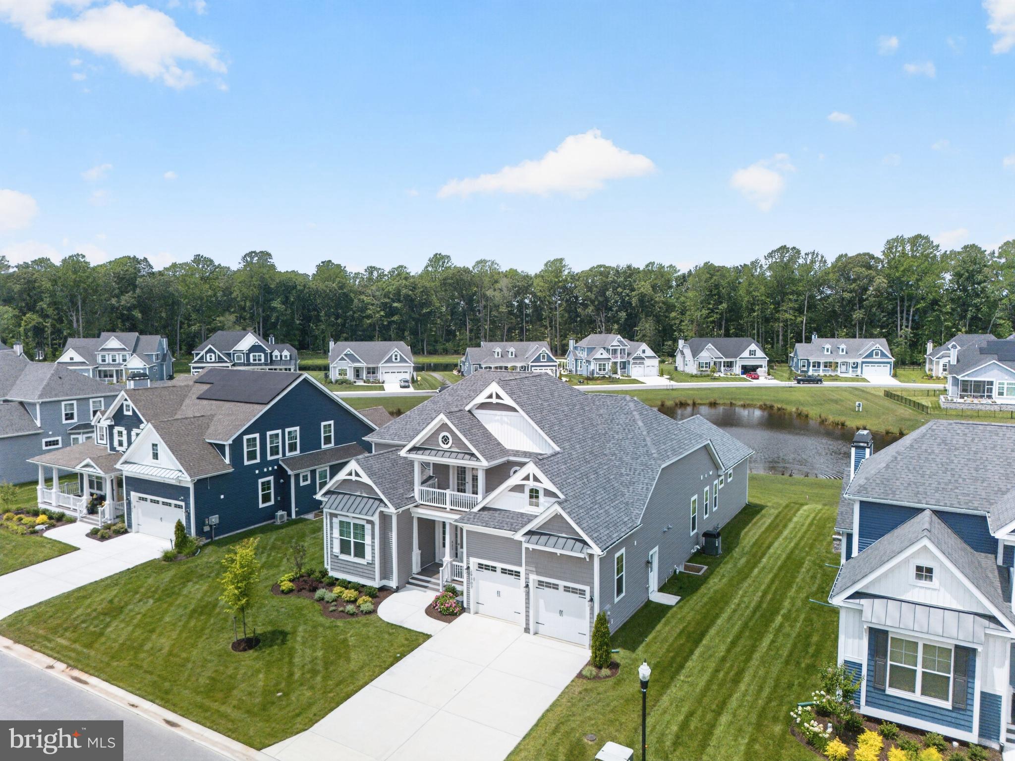 Completed in 2025 and positioned on one of Miralon's premier pond-front homesites, this exceptional Cassidy offers the luxury of new construction without the wait, complete with extensive designer upgrades already in place. This thoughtfully designed home features four bedrooms, four full baths, a powder room, private office, loft, and exceptional indoor and outdoor living spaces.

A welcoming covered front porch leads to an impressive foyer where engineered hardwood flooring, plantation shutters, and custom finishes set the tone throughout. Just off the entry are a private office with double French doors, a guest bedroom with a charming window seat, a full bath, and an oversized mudroom with abundant storage.

The dramatic great room features soaring beamed ceilings, a floor-to-ceiling fireplace, and walls of windows overlooking the pond. The gourmet kitchen is designed for entertaining with an oversized island, farmhouse sink, premium Wolf appliance package with Sub-Zero refrigerator, abundant cabinetry, a walk-in pantry with coffee bar, and a custom wet bar with beverage refrigerator adjoining the dining area.

The first-floor primary suite offers tranquil pond views, a spa-inspired bath with oversized walk-in shower and dual vanities, and two walk-in closets. Custom California Closet systems are featured throughout the home, including all bedroom closets and the pantry. A private guest suite with its own bath, a well-appointed laundry room with custom cabinetry and utility sink, and a powder room complete the first floor.

Upstairs, a spacious loft opens to a covered balcony and is complemented by a fourth bedroom, full bath, and more than 300 square feet of unfinished walk-in attic storage, providing exceptional flexibility for future expansion or storage.

Outside, the expansive paver patio creates the perfect setting for entertaining or relaxing while overlooking one of the community's most desirable pond settings. The oversized garage includes an electric vehicle charging connection.

Miralon offers resort-style amenities including scenic walking trails, an outdoor pool with sun ledge, sauna, pickleball courts, fitness center, and built-in grilling area, all just minutes from Lewes, Rehoboth Beach, shopping, dining, and everything Coastal Delaware has to offer.