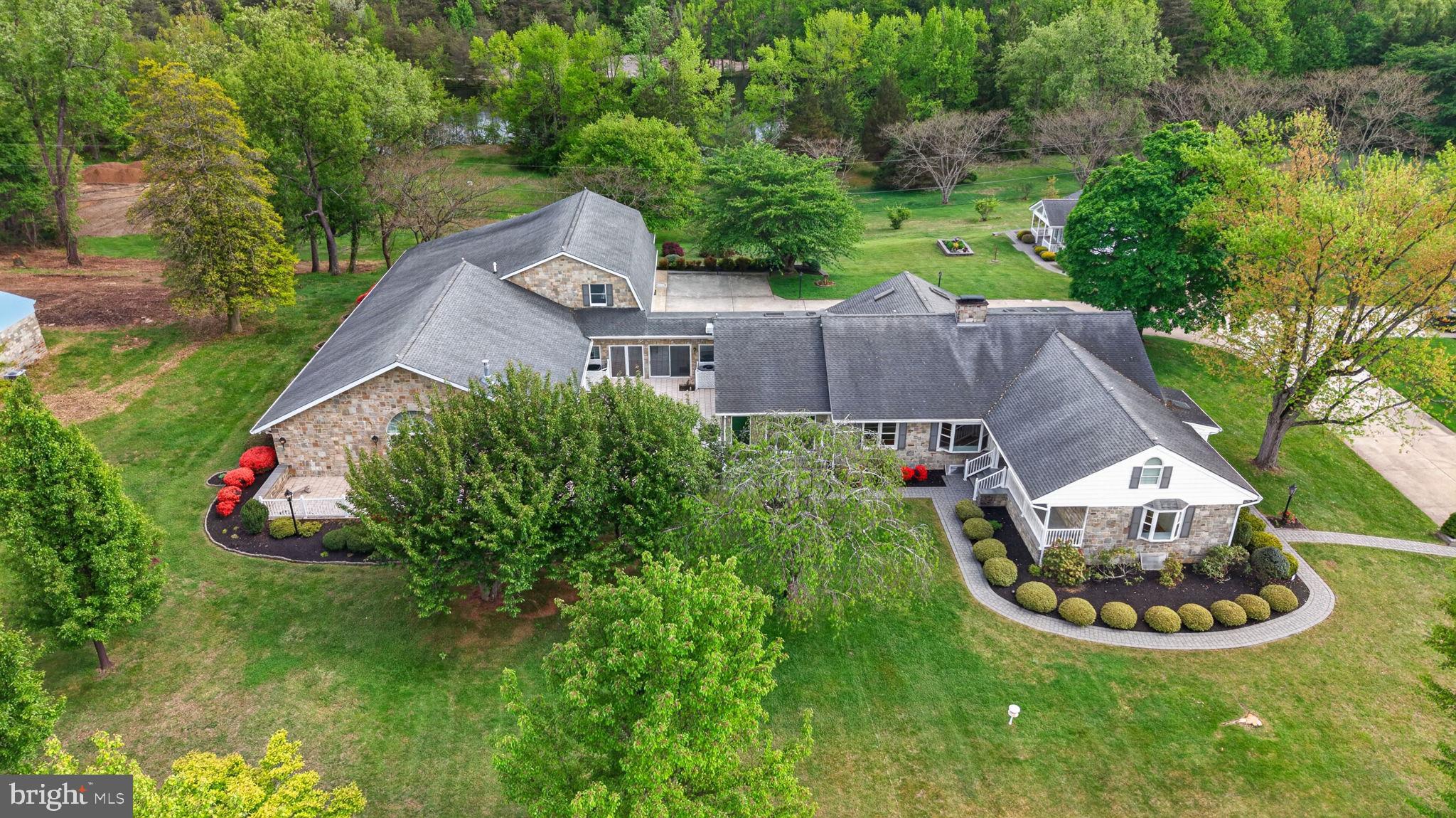 Set on over two private acres, this exceptional estate offers a rare blend of luxury, space, and serene natural surroundings. A dramatic, landscaped entrance and private driveway create a striking first impression, setting the tone for what lies beyond. Overlooking a picturesque pond, the property provides a peaceful setting with captivating views from every angle. Rich in history, this distinguished property, known as the Hamilton Residence, was crafted by builders renowned for their exceptional quality and enduring craftsmanship. Their legacy is evident in every detail, lending a meaningful sense of heritage to this already remarkable home. Offering nearly 10,000 square feet of thoughtfully designed living space, the home showcases a timeless Butler stone exterior, complemented by premium Andersen windows and doors that fill the interiors with natural light. Inside, high-end finishes throughout seamlessly blend elegance with functionality. An impressive addition introduces a private, separate wing anchored by an extraordinary primary suite - an inviting retreat featuring sophisticated molding, refined finishes, and its own full-size basement, ideal for additional living space, a fitness area, or extended storage. Recent renovations have thoughtfully prepared this home for today’s market, including fresh paint throughout, new flooring, updated baths, refreshed kitchen touches, updated lighting, an upgraded lower-level kitchen, and enhanced landscaping. Recently refinished hardwood floors add warmth and character, while expansive living areas provide the perfect backdrop for both everyday living and entertaining. An oversized three-car garage and abundant storage options ensure convenience without compromise. Positioned along the driveway and overlooking the tranquil pond, a charming studio/cottage offers a unique and versatile extension of the property. Complete with a half bath and sink, this detached space is ideal for gardening, a private studio, guest overflow, or a peaceful retreat. The cottage also presents the perfect opportunity to serve as a future pool house, with the perfect setting for a custom pool overlooking the tranquil pond and surrounding landscape. This is a rare opportunity to own a truly special estate where craftsmanship, scale, history, and setting come together in perfect harmony.