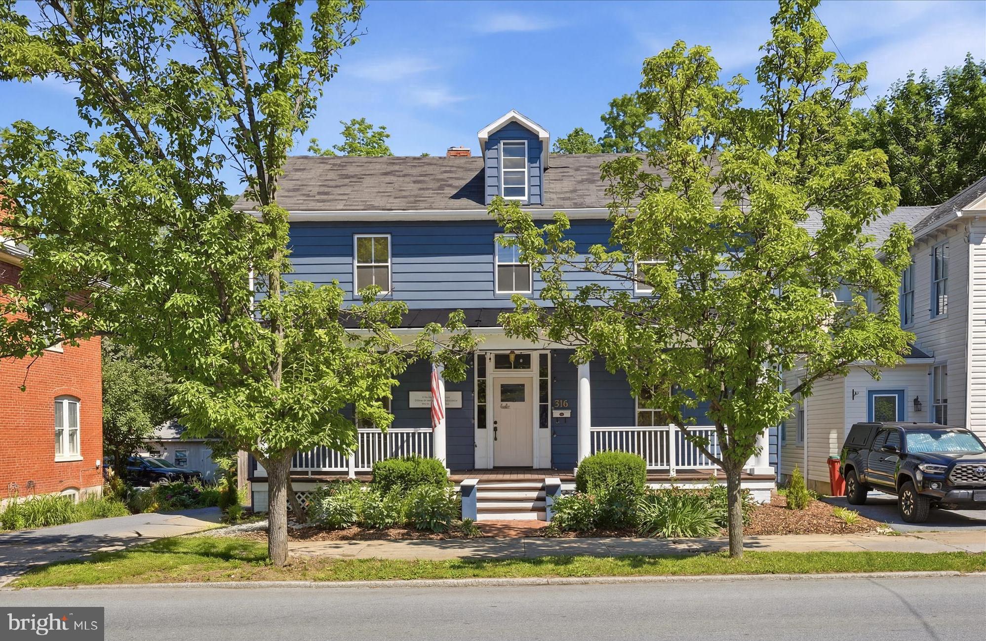 Step onto the front porch, settle in for a minute, and you can feel what makes this downtown Charles Town home different. Built circa 1900, it carries the kind of character that only time can create, with original hardwood floors, handsome wood wainscoting, and rooms that feel warm, grounded, and full of personality. Inside, the kitchen is the showpiece and the heart of the home, with floor-to-ceiling forest green custom cabinetry, a farmhouse sink, professional-grade range, stained glass accents, and soapstone countertops that give the space a collected, designer feel. The living room is bright and inviting, with natural light pouring through the windows and views of the tree-lined street just beyond. Upstairs, the primary bedroom is generously sized, filled with light, and wrapped in the same rich wood details that make the home feel cohesive and authentic. Out back, the private deck and patio open to a fully fenced yard that adds both function and freedom, whether for outdoor time, gardening, or room for dogs to roam. From morning coffee on the porch to an evening walk to dinner, boutiques, or the farmers market, this is a home that connects historic charm with the rhythm of downtown living. Basement storage, a full laundry room, and attic space complete a layout that is as practical as it is memorable.