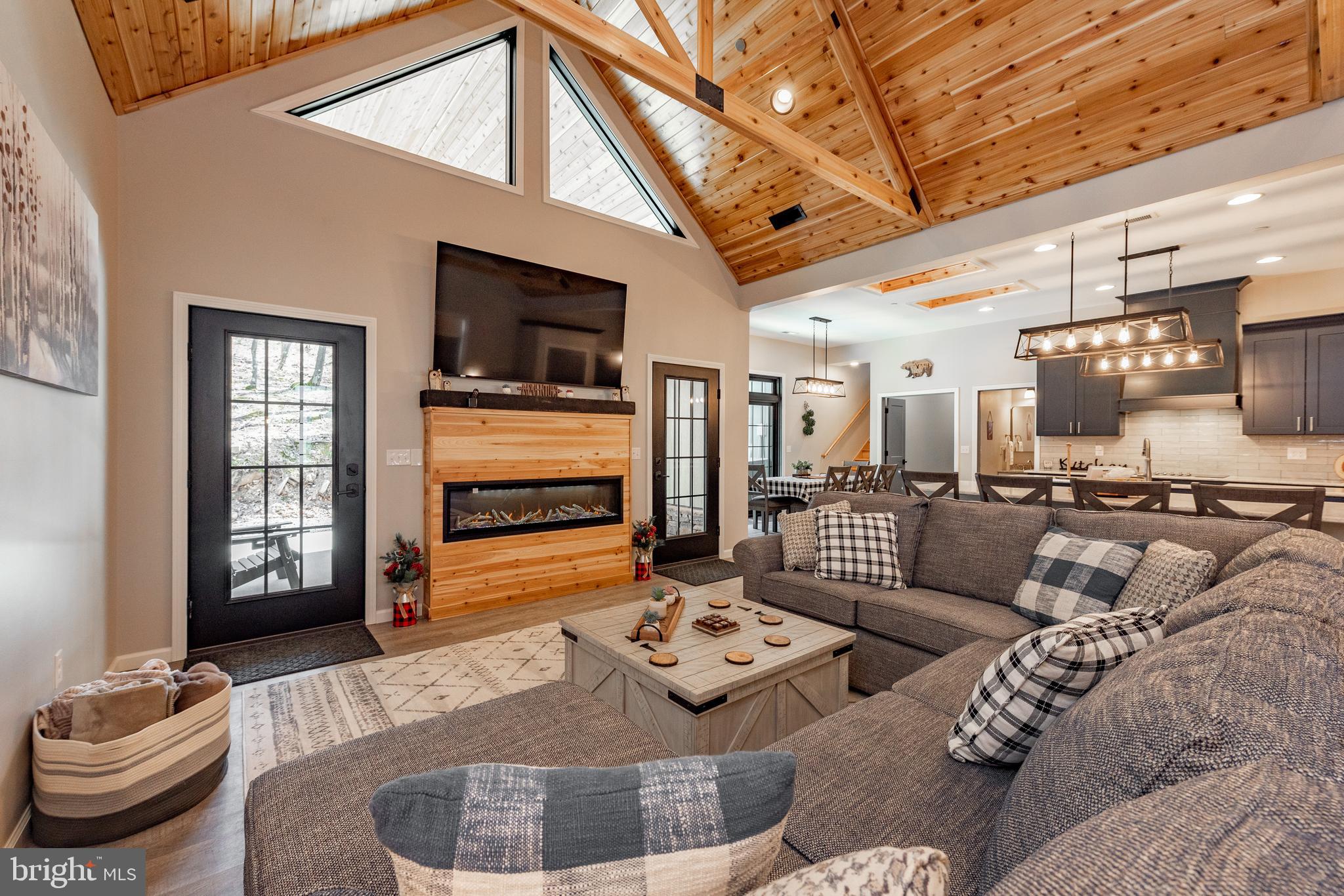 Luxury mountain retreat in the heart of Deep Creek Lake! “Ski Time to Tee Time” is a spacious 6-bedroom, 6.5-bath home offering the perfect blend of rustic elegance and modern comfort, ideally located near Wisp Resort, Lodestone Golf Course, and Deep Creek Lake. Inside, soaring cathedral ceilings with exposed wood beams and a stunning fireplace anchors the expansive open living area, creating a warm and inviting atmosphere for gathering year-round. The gourmet kitchen is designed for entertaining with dual islands, abundant prep space, and seamless flow into the dining and living areas. Multiple entertaining spaces throughout the home provide room for everyone to relax, including a garage-turned-game-room complete with a pool table and entertainment space. The home also features an EV charger for added convenience. Step outside to enjoy the hot tub under the stars, spacious outdoor living areas, and peaceful mountain surroundings. An established vacation rental with strong investment potential, this property also serves as an exceptional personal getaway. Whether you're searching for a primary residence, second home, or income-producing retreat, this Deep Creek property delivers luxury, recreation, and convenience in one of the area's most sought-after locations.