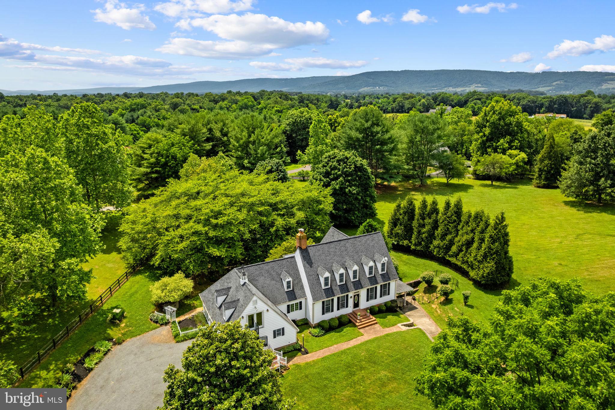 Hidden Hill is a stunning property that offers nearly 5,000 sq. ft. of living space, providing an unparalleled level of privacy and tranquility. With two full separate living spaces featuring private entrances, this residence is ideal for multi-generational living. The main level showcases hardwood floors throughout, featuring a formal living room, an inviting family room with a wood-burning fireplace, and a spacious dining room perfect for entertaining. The gourmet kitchen, complete with an eat-in area, leads to a sunroom that bathes the space in natural light. The main level primary suite offers comfort and convenience, and the two-car garage, ample storage. Upstairs, discover three generously sized bedrooms and a full bathroom, complemented by an upper-level apartment, that boasts an expansive open space with a kitchen, full bathroom, and gas fireplace. Skylights enhance the bright ambiance, and a separate spiral staircase leads directly to the exterior, ensuring both privacy and accessibility. The lower-level apartment, featuring a walkout entrance, includes its own kitchen, living room, bedroom, and full bathroom, creating an ideal guest suite or in-law accommodation. The outdoor spaces are equally impressive, with stone wall landscaping and a side patio perfect for relaxation. This tranquil oasis is complete with two garden sheds and no HOA restrictions, allowing for endless possibilities. Experience the perfect blend of seclusion and comfort in this exceptional property—a true hilltop retreat.
