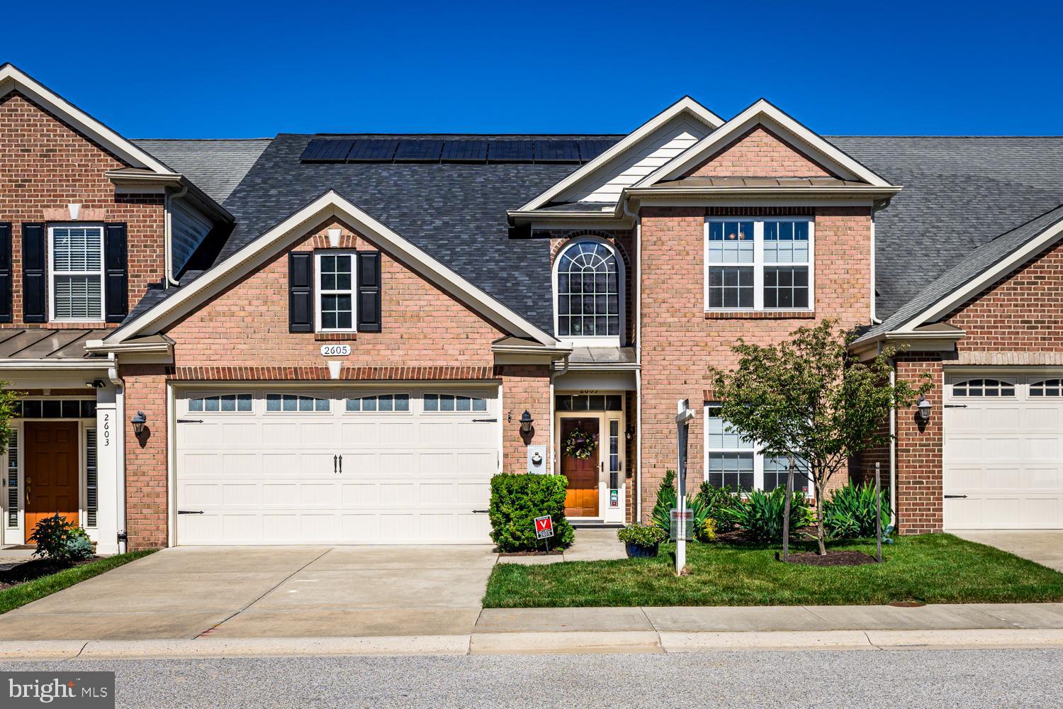 This brick front beauty is located in the desirable 55+ neighborhood, The Enclave at Ellicott Station. Upon entering you will be greeted by a two-story grand foyer with hardwood floors that carry through most all of the main level. The adjacent separate dining room is enhanced with both chair and crown molding and shares an open pass through to the gourmet kitchen which serves as the heart of this home. Stainless steel Jenn Air appliances, a down drafted gas range and granite countertops surround the oversized granite topped center island. Both the kitchen and island seating area are wide open to the cozy family room with a gas fireplace, ceiling fan, and included wall mounted television. Stepping past the family room, the new homeowner will immensely enjoy their fully finished, climate-controlled sunroom with ceiling fan allowing you to open up and enjoy the fresh air on cooler days. There are also plenty of open deck area for getting your morning dose of vitamin D and alfresco dining. The main floor primary suite is fit for a king, sized bed that is with plenty of room to spare! It features an expansive walk in closet and a spa inspired luxurious bathroom with double sinks, a private water closet, a walk in shower and a separate soaking tub. The versatile upper level lends to many different usage options, boasting three spacious bedrooms, a full bathroom and an open living area overlooking the foyer as well as a large storage closet. The daylight lower level with its walkout exit adds even more bright and functional living space including a fifth bedroom, full bathroom, second family room with included wall mounted TV, a massive storage room and a workshop area. Outdoors, the fenced backyard features a paver patio and mulched perennial beds with direct access to lush green space and community walking trails. Modern upgrades include owned solar panels, EV chargers, two Tesla battery storage units, and Maryland-themed garage floor tiles. Homeowners can opt to further enhance their daily living by enjoying the scenic walking paths and utilizing the community’s well-appointed clubhouse offering a fitness room, kitchen, game room, gathering space, patio and gazebo.  See details in photos and documents for Solar Savings and Improvement List.