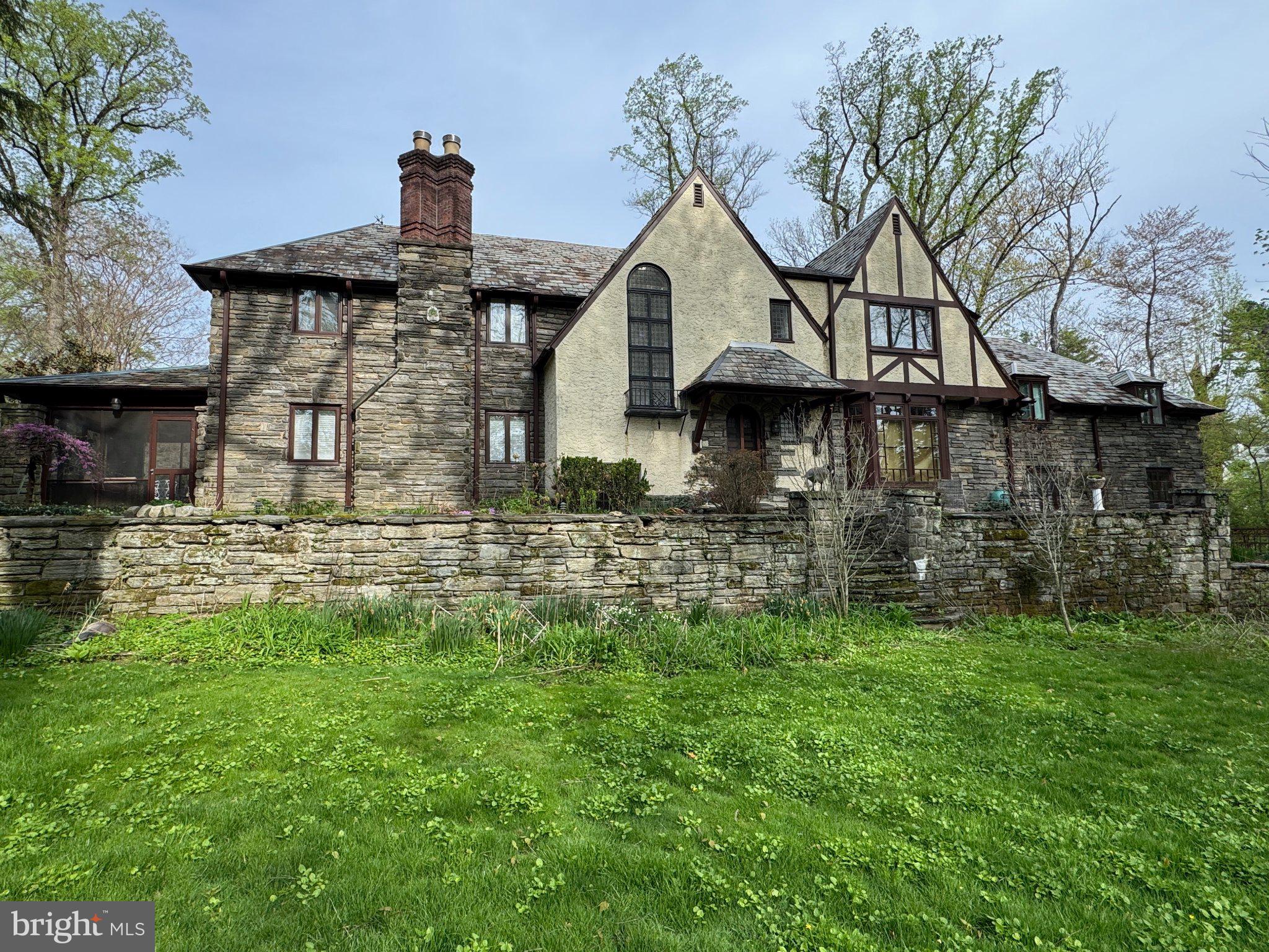 Classic Tudor home offered for sale for the first time in over 50 years. Custom built in 1927, this stunning stone and masonry mansion sits on a lush and private .57 acre corner parcel in the center of Wynnewood Valley. Outstanding classic details include all plaster walls and ceilings, custom mill work, built-ins, soaring leaded glass windows, exquisite brick estate style chimneys, grand curving main staircase, all wood doors, 2 fireplaces including custom Mercer Tile surround in living room. Updated kitchen with Sub Zero refrigerator, gas cooktop, door to back stairs and outside access to attached garage. Breakfast room with built-in bench seating and bright bay window. Cozy den off kitchen with built-in bookcases and storage and access to driveway. Formal dining room with wall of updated windows overlooking front patio and yard. Large living room with recessed lighting and Mercer tile fireplace surround and 2 doors to screened in porch. Enclosed entry vestibule with lower level access leads to two story foyer featuring a formal powder room & coat closet with doorways leading to living room, den and dining rooms; ideal for entertaining. Grand sweeping stairway to 2nd floor landing overlooking foyer below. Large primary bedroom suite with private bath and 2 closets. Three additional large bedrooms, a large office, small den, laundry room and hall bath complete second story. There is both walk-up and pull down stair access to ample attic space. Lower level has family room, great room with fireplace, wine cellar, powder room and large mechanical/storage area with direct access to rear of garage and stairs to covered breezeway between garage and rear driveway. Outside are several stone patios, stone lined driveway, wood bridge over small stream running alongside park-like grounds providing privacy and ample play space. This is a unique opportunity to own a one-of-a-kind classic Main Line Tudor estate in a coveted section of Lower Merion Township.