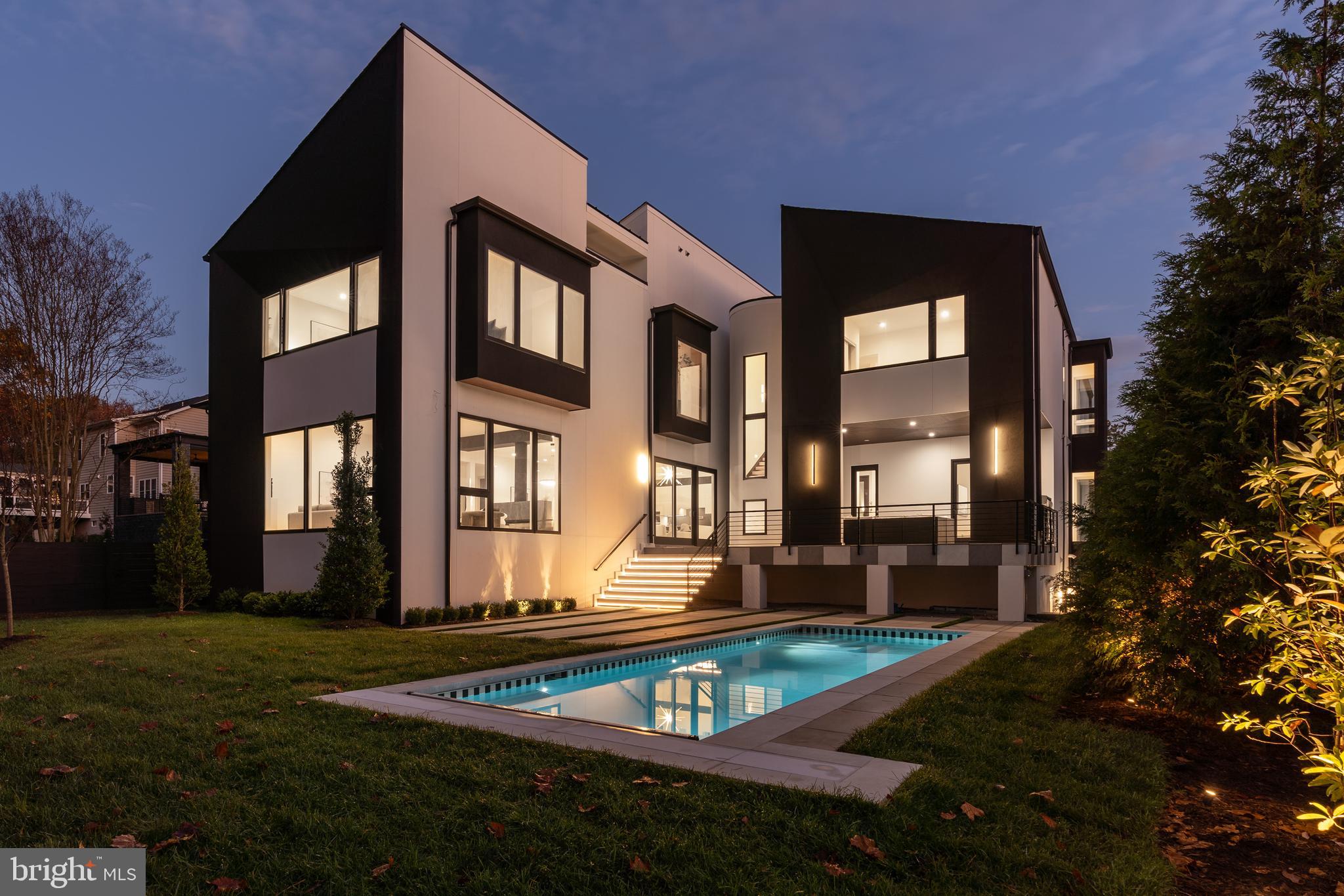 This architectural masterpiece will take your breath away as soon as you arrive at the address and gaze upon its incredible and warm modern construction, stucco exterior, and slanted roofs. Situated on a sprawling flat lot in McLean, this impressive property is the masterpiece collaboration between a talented architect, Charles Owen - a prominent landscape architect, and proudly built by Corebuild+. The delights continue as you step inside onto the light natural oak hardwood floors and be captivated by the intuitive design, walls of glass, state-of-the-art details and luxurious finishes that this home offers.  Featuring three floors, seven bedrooms, seven bathrooms, one half bath, and a 2-car garage conveniently situated on the main floor, with a total living space of 7,982sqft.  A living room with a 2-sided fireplace, 2 offices, a theater room, a gym,  wine storage room, elevator ready, pool + pool changing-room. are amenities that are sure to impress.  
The main owner's suite is truly a dream come true, nestled on the east-wing of the property, featuring his/her walk-in closets, an elegant fireplace, soaring ceilings, and a private terrace, where you can enjoy the magnificent views. Plus, the spa-like main bathroom is nothing short of a five-star resort experience, with its high-end fixtures, skylight, and luxurious details. This owner's suit comes with its own secluded extended seating area,  and an outdoor yoga studio. 
This home features two kitchens; a 2-story family kitchen complete with commercial grade appliances offering a large island with ample storage space, and a catering kitchen with a pantry - a true entertainer's dream! The main level offers a spacious and private ensuite guest room. The lower level includes a recreation room equipped with a bar/kitchenette, as well as a concrete bunker designed as a safe room.
 The rest of the bedrooms are equally spacious and comfortable, and all feature ensuite bathrooms, to maximize privacy and convenience.  The cherry on top is the professionally designed outdoor’s space, featuring an outdoor kitchen, a backyard with professional landscaping and a sparkling in-ground pool. This spot will be perfect for outdoor entertaining, or to enjoy by yourself as a secluded, Zen-like paradise.  Other features of this fantastic modern property include multiple terraces, a CIRCA designer lighting package, and a built-in audio system.  Ideally located in a friendly neighborhood, you'll be just a short drive away from downtown DC and a 5-minute drive to Tysons Corner shops, restaurants, hotels, and professional offices. There's truly nothing missing in this masterfully designed gem; this home is thoughtfully designed to inspire and elevate human soul!