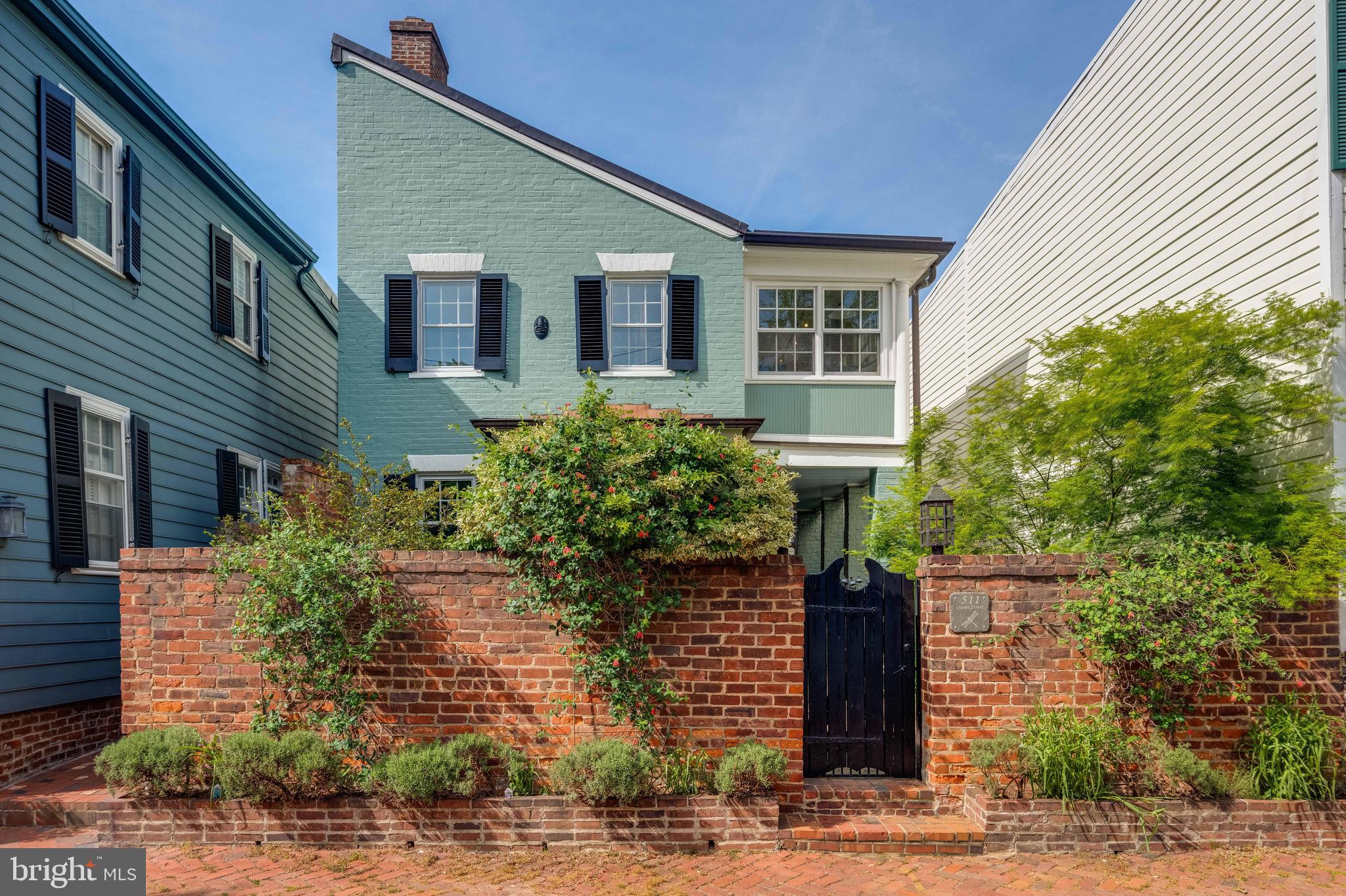 Step into a world of timeless elegance and contemporary luxury with this charming historic brick "flounder" in Old Town. Set on a rare 4,000 sf lot and surrounded by natural light on 3 sides, this home and its meticulously curated gardens provide a serene retreat in the heart of an urban village. 
Originally built in the late 1700s, it has undergone a comprehensive restoration and renovation over the past 20 years, all while maintaining the authenticity of its historical character to the most minute detail. As you cross the front door's threshold, you are immediately transported to a bygone era. The architectural features, design elements, and overall ambiance evoke a sense of history and nostalgia that seamlessly blend with modern touches. The unique entrance door, handcrafted with pegs - not a single nail - from wormy chestnut dating back to 1800, and the solid brass dolphin door knocker that reflects the maritime heritage of Alexandria are just a few examples of the exquisite care and attention given to this home. The interior is equally captivating, with 5 restored fireplaces, original heart pine floors, and many other original features brought back to modern standards. Upstairs, improvements such as the custom built-in marble topped dresser, comfortably renovated sunroom/office, and updated bath offer functionality and character. The first level of the addition smoothly unites history, craftsmanship, and culinary artistry. This harmonious fusion of design influences reflect the owner's culinary career, artistic education in the US and Italy, and travel through Europe and the UK, creating a space that is both aesthetically pleasing and inspiring. Modeled after the British "unfitted" kitchen, it begins with the eat-in dining area, complete with original colonial fireplace, restored to its former glory and effortlessly integrated into the space. The kitchen is outfitted with high-end appliances and chef-designed storage areas adjacent to the center island. This island is the heart of the kitchen and will surely delight the most discriminating chef. Composed of three different work surfaces, the island offers a kidney-shaped Carrara marble surface for pasta and pastry, a slate counter and hammered nickel sink for vegetable prep, and a kidney-shaped maple and walnut cutting board for preparing meats and fish. Woods from Europe and the US create the custom cabinetry designed to fit all of your kitchen tools and equipment. No doubt it will become your perfect setting to cook, entertain, and spend evenings with friends and family. The den is situated at the far end and offers a cozy, inviting space to entertain friends, unwind, read, or enjoy a relaxing cup of tea. Its proximity to the work area allows for guests to engage with the chef as their meal is prepared, with a serene view of the garden through the French door. The addition's back staircase leads to an incomparable Primary Suite. Its bedroom features reclaimed wormy chestnut floorboards, a Juliet balcony overlooking the extensive rear garden, and a meticulously restored paneled pine door with a hand-forged handle and knocker from the early 1800s. The Primary Bath is an award winning masterpiece in contemporary design, featuring a custom-made Japanese stainless steel soaking tub with two waterfall faucets, glass-enclosed rain and hand-held showers, and heated tumbled slate floors. The transition room from the original home to the addition on this second level was converted into a spacious walk-in closet with custom cabinetry, ample shelving, clothes hanging sections, and a dedicated laundry area.
This luxurious historic home is truly an individual, creative interpretation, meshing history and
contemporary elements, offering a one- of-a-kind, artistically-inspired living space. Designed to create an
enchanting, peaceful retreat amidst an oasis of lush gardens and the sounds and scents of nature, it will
surely leave a lasting impression on all who visit it.
