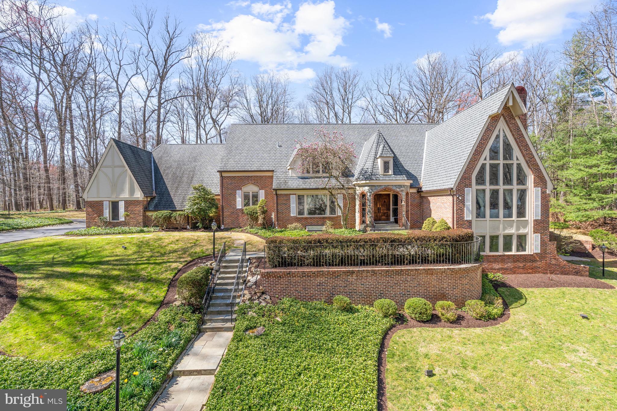 Newly Priced & Ready to Go! Soaring ceilings and light-filled rooms are the hallmark of this spacious 10,000+ square foot home just a few miles from the shops, restaurants, and other amenities of Potomac Village. Located on a beautiful two-acre, wooded lot, this serene and tranquil setting is located in the sought-after Potomac Village Estates neighborhood.
The main level offers a highly desirable two-story primary suite with a loft area perfect for a quiet workspace or library, sitting area, and a fully renovated bathroom with an electric fireplace, two walk-in closets, and an oversized marble shower that can easily accommodate two!
Also located on this level are a large living room with cathedral ceiling, wood-burning fireplace, and two-story wall of windows; dining room; library; and great room that also has a cathedral ceiling and wood-burning fireplace. The kitchen has been renovated to reflect today's active lifestyle with a large center island with pendant lighting and eating space, lots of cabinets with granite countertops, and top-of-the-line appliances. The sliding glass door opens to the back yard with a 1,700 square foot flagstone patio and recirculating fountain, perfect for outdoor relaxation or entertaining.
The upper level provides an abundance of space as well, with four bedrooms and two full bathrooms. One bedroom is adjacent to a sitting room or bonus room with its own staircase to the first floor.
The walkout lower level offers the potential for a variety of living options. A large recreation room boasts a wood-burning fireplace and a curved brick bar with granite countertop that can also serve as an additional kitchen. There is also a bedroom, now being used as a gym, and full bathroom,  a wine cellar, plenty of storage space, 
This fabulous home enjoys easy access to 1-495 and 1-270 as well as Washington, DC and Northern Virginia. Area residents can take advantage of the fine Montgomery County schools in the Winston Churchill Cluster as well as notable private schools. Recreation possibilities abound with a number of nearby public parks and golf courses.