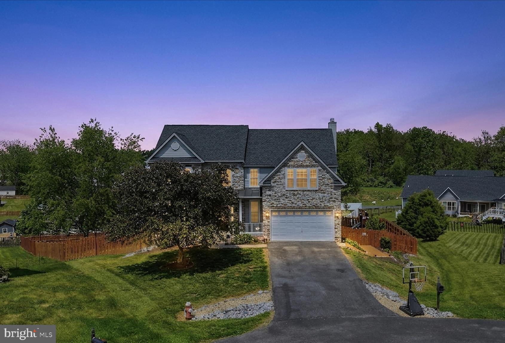 This remarkable Colonial combines impressive scale, refined finishes, and exceptional outdoor living in an elevated cul-de-sac setting with a fully fenced oversized backyard. Extensive hardscaping highlights the outdoor spaces, including a dramatic two-story covered deck, a lower-level pergola-covered deck, a stone patio with a built-in firepit, retaining walls, and dedicated exterior storage.
Inside, a grand two-story foyer opens to rich hardwood flooring that extends through the sitting room, formal dining room, and spacious family room centered around a striking wood-burning stone fireplace. The kitchen features granite countertops, abundant cabinetry, and a double oven range, while the adjoining morning room provides access to the covered deck overlooking the surrounding landscape.
The upper level is anchored by a spacious primary suite with vaulted ceilings, a large walk-in closet, and a spa-inspired bath featuring dual vanities, a soaking tub, a walk-in shower, and a private water closet. Three additional generously sized bedrooms and a full bath with dual vanities complete the second floor.
The fully finished walkout lower level adds substantial living space with a large recreation room, versatile bonus room, full bath, storage area, and direct access to the lower deck and backyard. Additional features include a Culligan water conditioning system, reverse osmosis kitchen filtration, home security system, structured wiring panel, and Nest Learning Thermostats, offering a blend of comfort, functionality, and thoughtful upgrades in one of Jefferson County’s most sought-after communities.