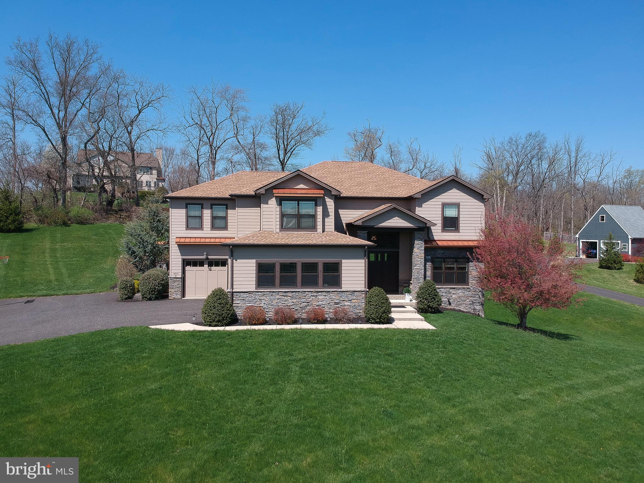 Welcome to this exceptional custom-built home by ASV builders, constructed in 2018, offering 5 bedrooms, 4.5 bathrooms, and beautifully curated living spaces that seamlessly blend timeless elegance with modern comfort. Nestled on 1.5 acres of meticulously landscaped, serene grounds, this property provides a private retreat with luxurious indoor and outdoor living. From the moment you arrive, the grand two-story foyer, adorned with rich hardwood floors and a refined sitting area, sets an impressive and welcoming tone. The formal dining room features an elegant coffered ceiling, creating a sophisticated backdrop for both intimate dinners and large-scale entertaining. At the heart of the home, the gourmet kitchen and bar area is a true showstopper, appointed with gleaming granite countertops, a striking stainless steel backsplash, and premium appliances. The sun-filled dining/breakfast area offers seamless access to the patio and flows effortlessly into the expansive two-story great room. Here, a dramatic floor-to-ceiling stone fireplace with a reclaimed wood mantel, soaring ceilings, and a breathtaking wall of windows combine to create a warm yet grand living space filled with natural light. A private office with sliding doors to the patio provides an ideal work-from-home environment or peaceful retreat. The thoughtfully designed first floor also includes a highly functional mudroom with custom built-ins, featuring a desk, shelving, and hooks to keep everything organized along with a powder room. Lighting and blinds on the first floor are fully automated, adjusting natural light. Upstairs, the luxurious primary suite serves as a tranquil sanctuary, complete with a ceiling fan, fireplace, an expansive custom-organized walk-in closet, and a spa-inspired ensuite bath boasting an oversized shower, soaking tub, and dual vanities. Two additional generously sized bedrooms share an adjoining bathroom, while a fourth bedroom with an en suite bath completes the second level. The finished walk-out lower level significantly expands your living space, offering a fifth bedroom, full bathroom, ample storage, and endless possibilities for recreation, entertaining, or guest accommodations. Step outside to your own private outdoor oasis, thoughtfully enhanced in 2019 with a covered porch with stone/slate flooring, pergola, outdoor kitchen, and fireplace, creating the ultimate setting for year-round entertaining or peaceful relaxation surrounded by nature.  The home is equipped with a central vacuum system for added convenience.  House features a 3 car garage.  Ideally located near Doylestown Boro, shopping, dining, major commuting routes, and situated within the highly acclaimed Central Bucks School District. This remarkable home truly offers the perfect blend of luxury, comfort, and convenience.