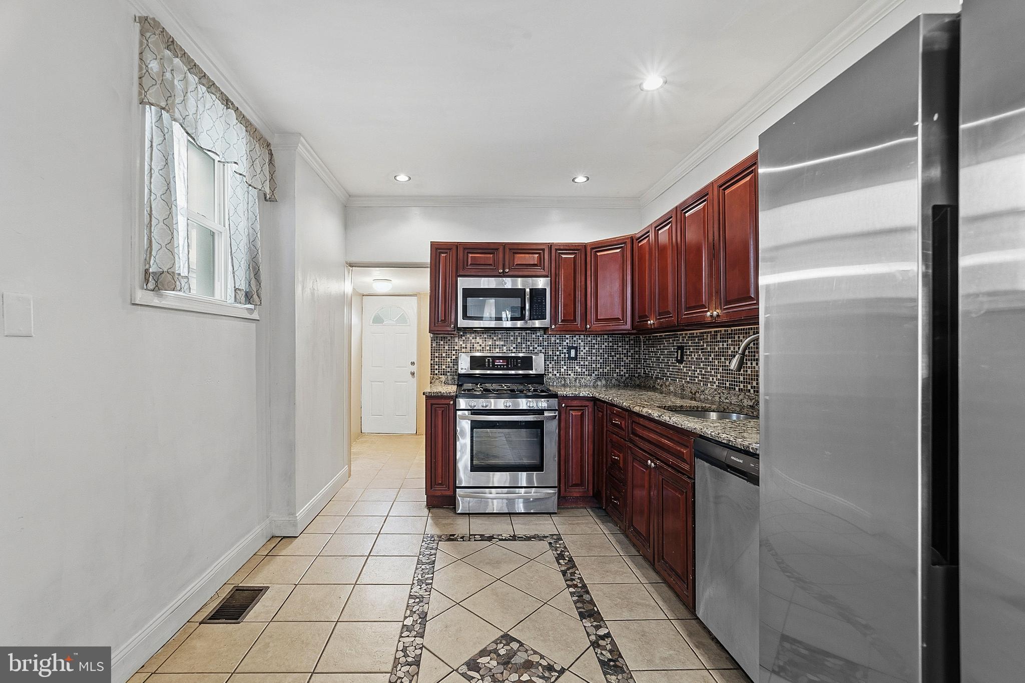 NEW PRICE! Welcome to this well-maintained, traditional row/townhome located in the Port Richmond section of Philadelphia, offering a blend of comfortable interior space, modern updates, and a convenient neighborhood setting. A covered front porch provides a welcoming entrance, while the beautiful view of the Philadelphia skyline from the street adds a unique urban backdrop. Inside, the main level features an open living and dining room combination enhanced by wood flooring, a bow window, ceiling fan, and recessed lighting, creating a bright and inviting environment for everyday living or entertaining.
The eat-in modern kitchen offers ceramic tile flooring, granite countertops, tile backsplash, honey-tone wood cabinetry, and stainless steel appliances, including a refrigerator, built-in dishwasher, built-in microwave, and gas range/oven. Completing the first floor is a full bathroom and an exit to the rear fenced cement yard, providing a practical outdoor space for relaxation or recreation. The fully finished lower level offers flexible living space suitable for a fourth bedroom, family room, or home office, along with a laundry area, updated PEX plumbing, gas hot water heater, and gas hot air heating system. The second floor accommodates a spacious primary bedroom with wood flooring and a sliding mirrored closet, along with two additional bedrooms and a three-piece hallway bathroom featuring a tiled stall  shower.
Residents enjoy proximity to several popular neighborhood destinations, including Campbell Square Park for outdoor recreation, the Richmond Street dining corridor known for local restaurants and cafés, and the nearby Aramingo Avenue shopping corridor, offering grocery stores, retail shops, and everyday conveniences. The location also provides easy access to I-95 and the Tacony-Palmyra Bridge, supporting convenient travel throughout Philadelphia and into New Jersey. This property offers a combination of functionality, updated features, and location within one of Philadelphia’s steadily evolving neighborhoods. Take a minute to view the Video Tour, and then Schedule your private showing, today. Some photos have been virtually staged/enhanced!