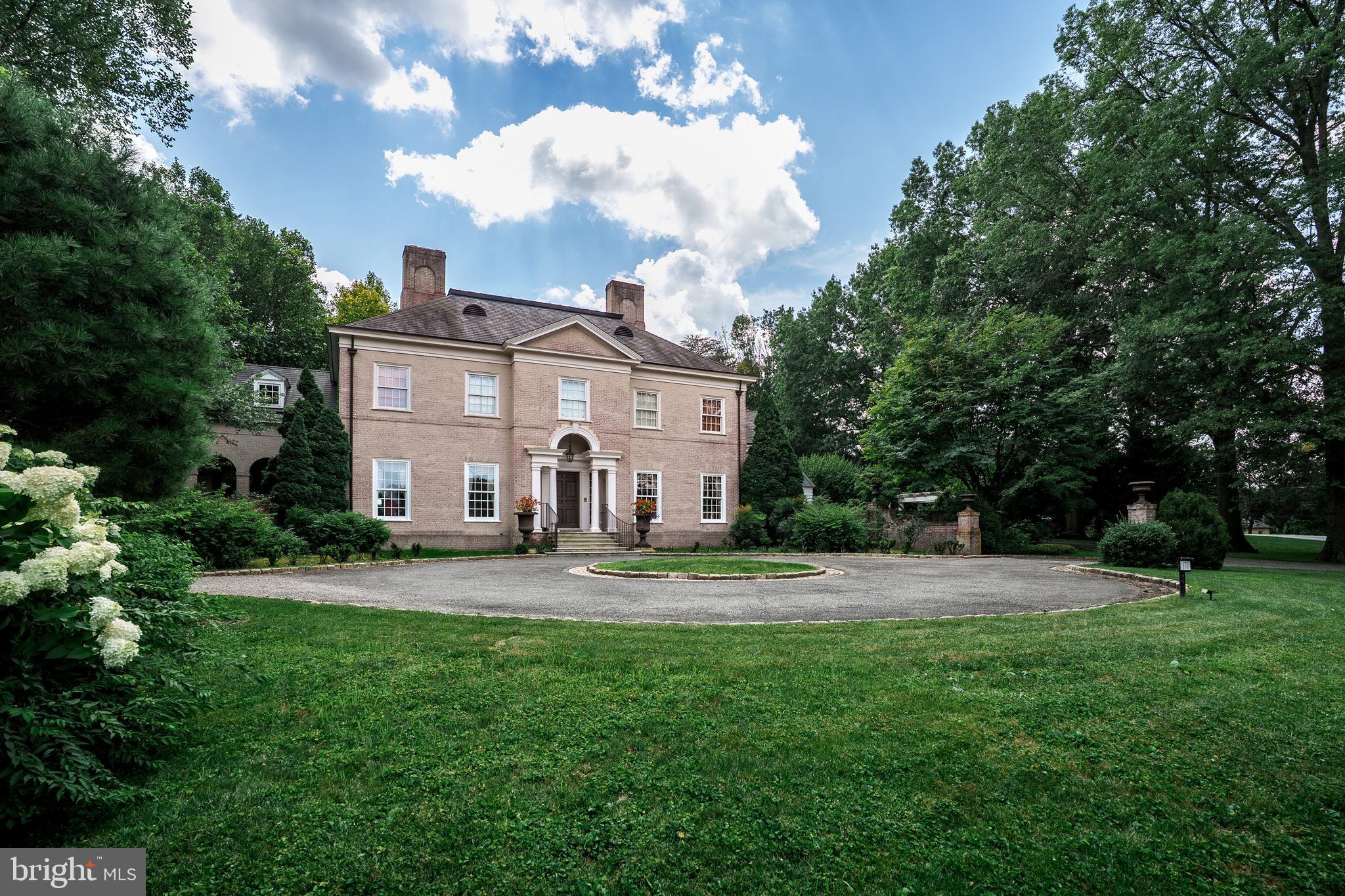 A tree-lined drive leads to the front entrance steps of the brick Georgian-style main house designed with exceptional attention to architectural detail and construction. The residence is designed to create an open and light filled warmth with 10-foot ceilings on the first floor, 9-foot ceilings on the second floor, and 14–16-foot cathedral-style ceilings with skylights and balcony on the third floor.  Together, 5 bedrooms with baths, two with fireplaces and balconies, a master bedroom with separate closets and dressing areas, and 3 half bathrooms provide ample comfort for family, friends and guests.  Centrally located in the School Lane Hills neighborhood, the home offers convenient access to shopping, services, recreation and entertainment.  

Main house highlights include custom woodwork and built ins, a marble-tiled columned foyer, powder room, grand double height stairwell with decorative plaster accents, formal living room with antique fireplace surround and separate marble topped wet bar leads to an outdoor bluestone porch and fireplace, cypress paneled family room with fireplace, build ins, and porch access, spacious, sun filled kitchen with double sinks, custom cabinetry, high-end appliances, marble counters and travertine flooring, formal multipurpose dining room with antique fireplace, build ins, and French doors leading to private walled garden, sun room w fireplace and build ins, family entrance to mudroom with 5 custom “cubbies”, wall-to-ceiling cabinetry, separate refrigerator, soapstone counter and sink,  a pantry with floor-to- ceiling storage, coat rack, stacked washer/dryer  and a floor height utility sink.   Lighting includes Waterford Crystal chandeliers in the dining room, custom accent lights, period-style fixtures throughout with exterior illumination provided by hand-crafted Carolina Lighting fixtures that enhance both the aesthetic and security of the property.  A separate office/exercise area and powder room complete the first-floor layout.  Throughout, “pocket” doors and hard wood floors provide aesthetic and practical complements for privacy and events.  The second floor includes 4 en suite bedrooms, a cozy reading space, and a large central laundry, with sink, crafts center and custom build ins.  

The extensively landscaped and mature plantings provide the 1.4-acre property with exceptional privacy and natural beauty.  Outdoor features include an in-ground swimming pool and waterfall designed with natural elements and plantings that blend into the landscape.  A spectacular blue stone slate plaza contains an enclosed seating area and fireplace and separate pool house with countertop, custom cabinetry, dishwasher, food warmers, refrigerator, and separate powder room and shower areas that together produce comfortable space for entertaining and relaxation. The three-car carriage house has a finished floor, storage systems and central vac and second floor living quarters with a kitchen, full bath, heating, cooling and central vac. 

This property combines classic Georgian architectural style with modern technology and conveniences. Centrally located but exceptionally private, the mature landscaping, spacious layout, quality finishes, and integrated systems offer a rare opportunity to own a home that balances traditional design with modern systems.  This property is designed to provide comfort and sophistication, suitable for everyday living as well as large-scale entertainment.