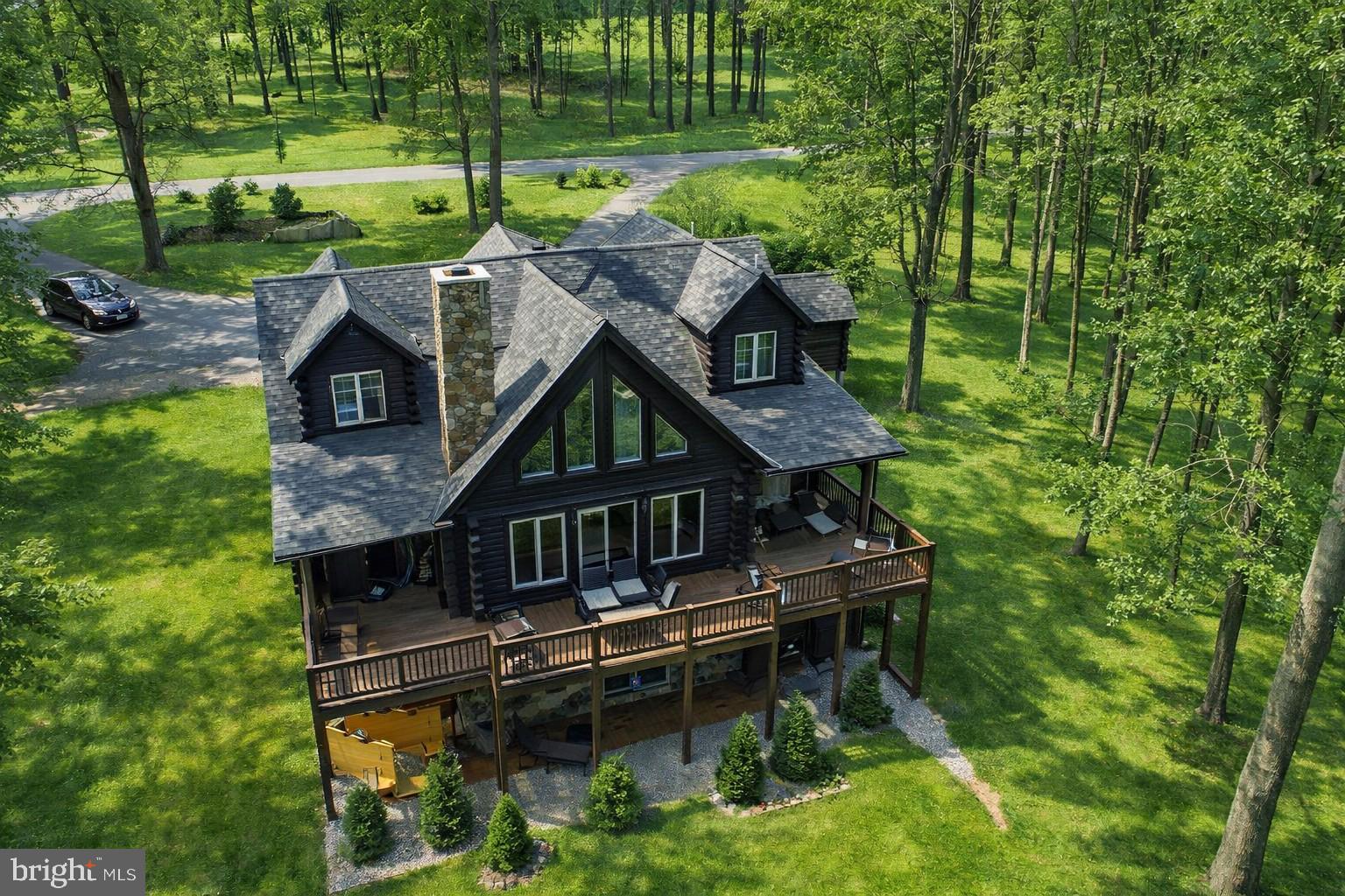 This stunning log home near Wisp Resort offers a luxurious retreat with seasonal views,  an indoor pool house and plenty of space for indoor and  outdoor living.  Five-bedroom, five-and-a-half-bath masterpiece is designed for both relaxation and entertainment. Step inside to discover an open floor plan adorned with exposed beams and rich wood floors. The gourmet kitchen, equipped with high-end appliances including a built-in microwave, wall oven, and cooktop, flows effortlessly into the dining and living areas, perfect for hosting gatherings. Cozy up by one of the two stunning stone fireplaces, or unwind in the fully finished walkout basement, which offers additional living space and direct access to the outdoors. Outside, indulge in your own private oasis featuring a newly upgraded fire pit area overlooking the private 1.46 acre wooded lot. Enjoy breathtaking mountain views and seasonal lake views from the expansive deck or patio, ideal for alfresco dining or morning coffee. Renters and primary residents alike will both love the indoor pool house to enjoy year-round.  Property offers a strong rental history!   With Deep Creek Lake, WISP Ski area and ASCI whitewater course just moments away, outdoor enthusiasts will appreciate year round activities. This property is not just a home; it's a lifestyle of luxury, comfort, and natural beauty. Experience the perfect blend of tranquility and sophistication in this remarkable residence.