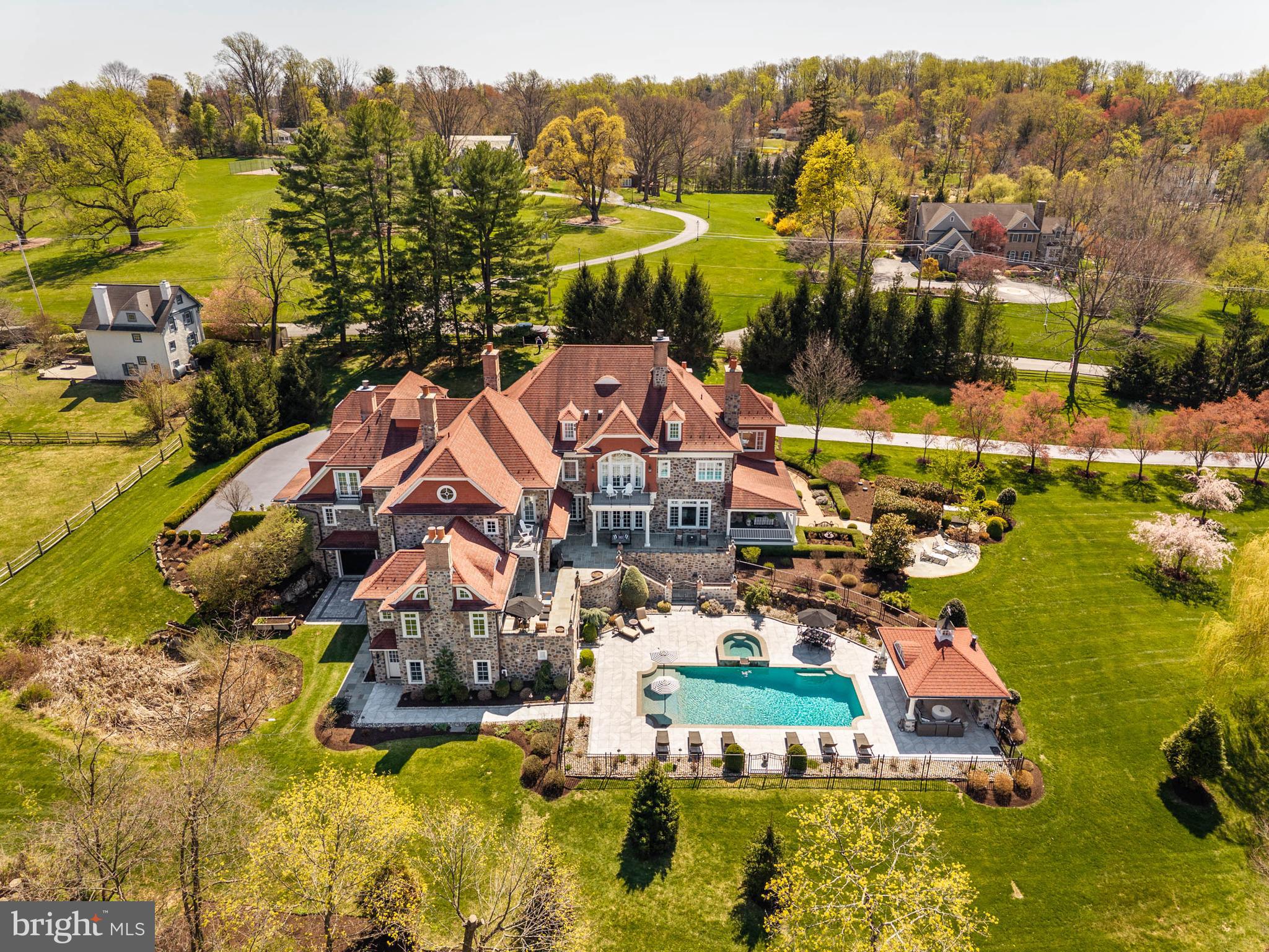 Set on approximately 12 acres, this exceptional stone home follows the tradition of the Main Line’s great country estates—designed for space, scale, and a lasting connection to the land. Built by highly regarded Ted Babiy of Diamond Construction, the residence reflects a level of craftsmanship and materials not typically found in newer construction, with architecture rooted in the proportions and detail of earlier homes.

A long, winding approach leads through stone entrance piers to a front courtyard, creating a gradual sense of arrival.

The entry opens to interiors marked by quality, warmth, and thoughtful design. The living room features a beamed ceiling, fireplace, and windows and glass doors on multiple exposures, filling the space with light and opening to the surrounding terraces. The dining room is grand in scale, with a coffered ceiling and two sets of French doors that open to a side courtyard with a fireplace, extending the dining space outdoors for entertaining.

At the center of the home, the kitchen, breakfast room, and family room connect seamlessly, designed for both everyday living and gathering. The kitchen is expansive, with a large marble-topped center island, custom cabinetry, high-end appliances, and a fireplace that anchors the space. The family room includes a fireplace and beamed ceiling, along with a distinctive inglenook seating area, creating a sense of comfort within its volume while opening directly to the terrace.

A sunroom provides a bright, inviting space framed by arched windows and French doors that open to the terrace, creating a direct connection to the outdoors. The first-floor home office features a vaulted ceiling, custom millwork, and a fireplace, combining functionality with architectural presence.

Multiple staircases and an elevator connect the main level to both the second floor and the lower level, supporting the home’s scale and allowing for efficient movement throughout.

The second floor includes seven bedrooms, including the primary suite and additional bedroom suites, with one currently used as an exercise room. The primary suite functions as a private retreat, with a vaulted-ceiling bedroom and fireplace opening to a balcony overlooking the grounds. A separate sitting room is wrapped in windows on multiple exposures, capturing sweeping views and light throughout the day. Dual baths and generous dressing areas complete the suite.

The lower level is designed as a full extension of the home’s living space, featuring a large recreation room, wet bar, home theater with custom seating, wine cellar, and a bath.

The outdoor setting captures the property’s long views. A rear flagstone wrap-around terrace—partially covered to create true outdoor rooms—extends from multiple interior spaces, including a covered terrace off the sunroom with a fireplace. Additional terraces, including one accessed from the family room, are positioned to capture those views.

Natural features—including a stream, arched bridge, and restored mill structure—add character and depth rarely found in combination on the Main Line.

The landscape is defined by sweeping lawn, mature plantings, and carefully composed gardens. A pool and separate cabana with outdoor kitchen and fireplace create a complete setting for outdoor living, all integrated seamlessly into the property’s surroundings.

A portion of the property is subject to a conservation easement with the Willistown Conservation Trust, preserving open meadows, mature trees, and natural habitat while limiting future subdivision. Details available upon request.

Properties of this scale, setting, and level of construction are increasingly rare—offering a combination of land, design, and craftsmanship that is not easily replicated.  Real Estate taxes are under appeal.