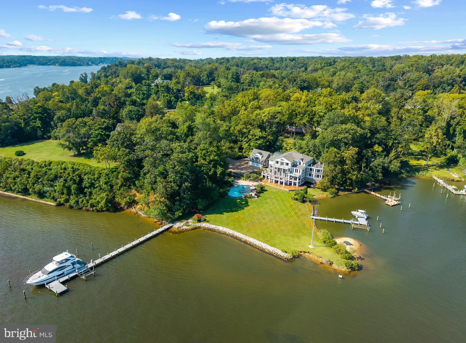 This Severn River estate is a rare opportunity to own one of the area’s most spectacular properties. Showcasing a negative-edge pool with beach entry and hot tub, 2 private piers to accommodate a variety of vessel sizes including a 100 ft slip, sprawling yard and sweeping views of the river and Naval Academy Bridge. Imagine waking each morning to the sun sparkling off the Severn, its reflection dancing across the water and spilling into a home designed to embrace the view at every turn. This extraordinary residence is both a private retreat and an entertainer’s dream, with expansive balconies and roof decks on every level, making indoor/outdoor living a breeze. Inside, soaring ceilings and walls of glass frame the ever-changing views like a living masterpiece, while the grand chef’s kitchen, stone-floored sunroom, and elegant dining spaces invite gatherings large and small. The primary suite is an entire level of indulgence, complete with soaring ceilings, a fireplace, spa-like bath, wet bar, expansive dressing room, laundry, and its own private balcony for starlit evenings. Additional ensuite bedrooms and a guest suite with kitchenette ensure comfort for family and friends, while the lower level—with wine cellar, kitchenette, and direct access to the pool—extends the living space to the outdoors. With a sandy beach and two private piers, one tucked into Crouches Cove and the other stretching into the Severn river, this estate offers not just a home but a lifestyle of breathtaking vistas on the water, boating adventures at your doorstep, and the unmatched beauty of Annapolis waterfront living. Located in the Blue-Ribbon Broadneck School district and just 5 miles to downtown Annapolis, convenient to Baltimore, BWI, Ft. Meade/NSA and Washington, DC., the location provides the very best this region has to offer in a 30-mile radius. If you are looking for a truly special property with EPIC water views, resort like amenities and a great private setting, this is the property you have been waiting for. Welcome Home!