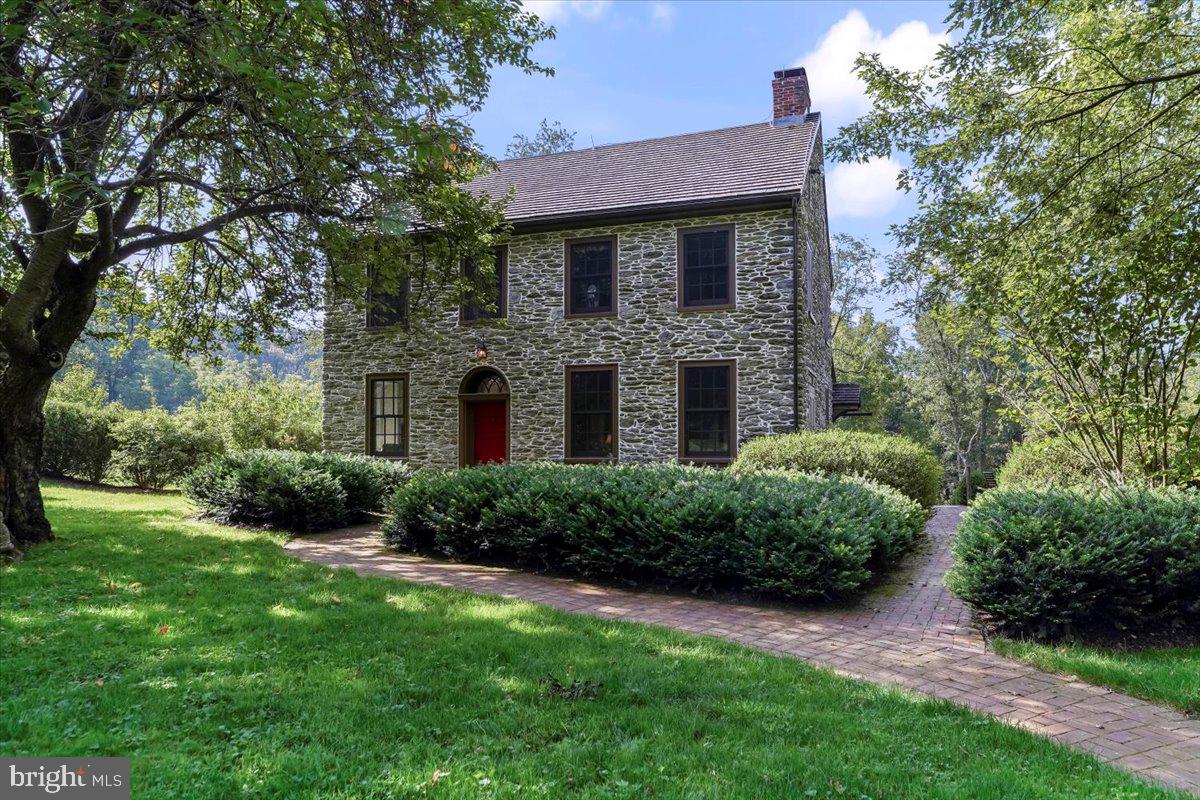 Steeped in the rich tapestry of Chester County history, the Mansel Passmore House offers a rare opportunity to own a piece of the past, thoughtfully reimagined for a sophisticated modern lifestyle. Originally constructed circa 1830 and listed on the National Register of Historic Places, this landmark residence anchors the storied Glen Rose Historic District. Over nearly two centuries, the home has undergone a series of masterful expansions, evolving into an estate that harmonizes its 19th-century soul with 21st-century luxury.
The journey begins at the circular drive that leads to the original stone structure. Inside, a formal Foyer warmed by a fireplace sets an inviting tone, flanked by a stately Living Room also anchored by a wood-burning hearth. The Main Level flows effortlessly into a private Den—featuring the home’s third fireplace—before opening into the sun-drenched heart of the home. The expansive Kitchen is a chef’s dream, centered around an oversized island with butcher block counters and a double sink. The professional gas range is where you will find the chef, while the sitting area and double french doors leading to the deck make this room the heart of the home. This airy space transitions seamlessly to a Breakfast Room with rustic exposed beams and custom built-in seating, while a dedicated prep area with stone counters and double wall ovens ensures the home is ready for large-scale entertaining. A Powder Room and Mud Room complete this level.
Retreating to the Second Floor, the Primary Suite serves as a private sanctuary flooded with southern light. This retreat features a reading nook, a private deck accessed through French doors, and a spa-like Full Bath with a soaking tub and separate shower, both offering serene views of the grounds. Two additional well-appointed Bedrooms, an attached Study,  an additional Full Bath and a convenient second-floor Laundry complete this level. The Third Floor offers a versatile escape, featuring an expansive Office drenched with natural light from a west-facing wall of windows, alongside a fourth Bedroom and a Full Bath.
The Lower Level extends the living space further, housing a comfortable Family Room that walks out to the rear yard, a fourth Full Bath, and ample storage. Beyond the main residence, the 5+ acre property is a masterclass in outdoor living. Multiple decks and terraces overlook mature trees, professional hardscaping, and protected neighboring lands. Adjacent to the main residence, the detached three-bay garage is a destination unto itself, with a charming Studio above that houses a fifth Bedroom and Full Bath—perfect for guests or a creative retreat. Attached to the Garage is the Bank Barn, complete with concrete flooring, running water, full electrical service and a half bath. This space is currently used as a professional-grade workshop, but is ideal for a multitude of uses.  An Office with a vaulted ceiling and exposed beams  attaches the Bank Barn and the Garage. The property is supported by a generator which powers a significant portion of the property. The sq. footage listed in all documentation is estimated and should be confirmed by the Buyer.  Of note, a portion of this property (2+/- acres) is under Brandywine Conservancy Easement.  Accessory structures are permitted, within the impervious limitations, on review and written approval of plans by the conservancy (paragraph 5 of the Easement provides detailed requirements for approval). Impervious limitations remain at 2.5% of the acreage (2,339 sq.ft). Complete with the original Springhouse and an equipment shed, the Mansel Passmore House is a testament to timeless architecture, offering a lifestyle of quiet elegance and historical significance.