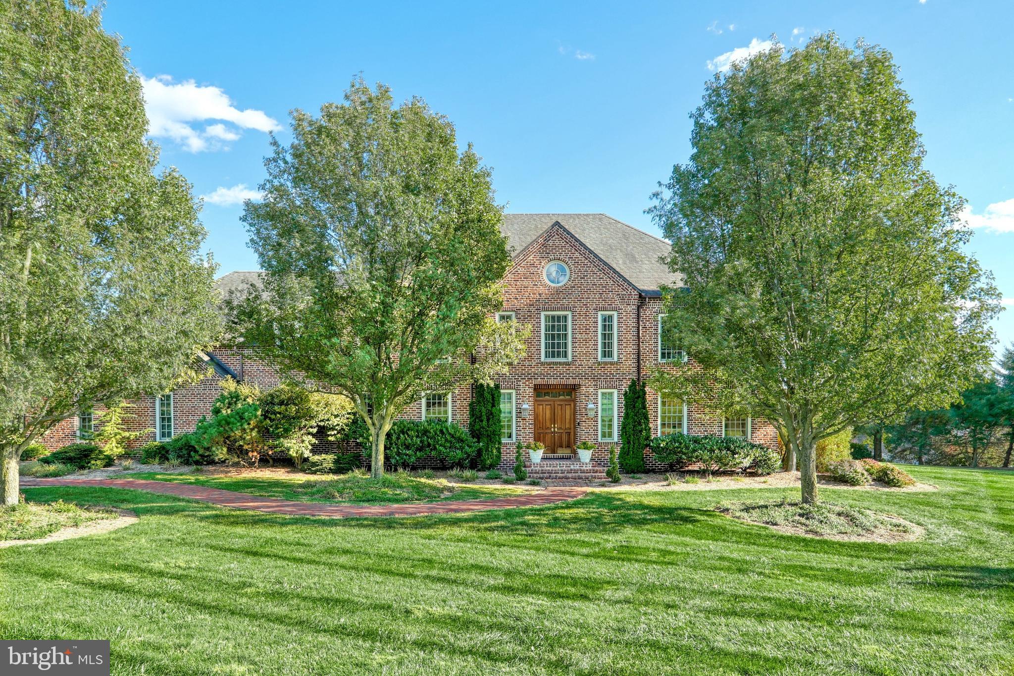 A Timeless Classic offering a premier location, best describes this custom all brick home sitting on 2.19 acres overlooking the Rosenmiller Farms. Designed and constructed with the finest finishes, this home has been professionally updated to showcase the meticulous care and pride of ownership.  As you enter the home you are welcomed by the stunning two-story foyer and a grand staircase. The home offers spacious light filled interiors accented by beautiful millwork craftmanship and stunning hardwood floors throughout the home. The formal living room features custom built-in bookcases and a stunning fireplace with marble surround. The formal dining room is perfect for entertaining and also offers the same quality of millwork and craftsmanship. The family room and kitchen areas feature an open concept design. The family room offers a beautiful open light filled room with wonderful windows to enjoy the views, custom built-in cabinetry and the perfect Stone fireplace to gather around. The spacious chef's kitchen with two islands, great spaces for prepping, great storage, granite countertops, new tile backsplash, updated light fixtures, a walk-in pantry, a beautiful bay front eat in area and so much more. From the kitchen eat in are you can step out to the stone patios to enjoy outside dining and entertaining.  Off the kitchen you will love the oversized laundry room and spacious hall to access to the rear of the home outside space. Access to the attached oversized 3 car garage that has an additional staircase to the lower level of the home for storage is located off this hall.  An additional feature of the first floor is a private first floor bedroom with a private bath. Perfect for guests.  The second floor of the home features the primary en-suite with multiple walk-in closets, an updated primary bath with separate shower and tub. Part of this wing of the home offers a private den/office with custom built ins and beautiful views.  There are three additional bedrooms on the second floor, all with their own en-suite baths. One bedroom offers a private balcony. All the bedrooms feature wonderful closet space with organizers. There is second staircase from the bedrooms to the first floor of the home.  The lower level of the home is also exceptional. There is a large game room with a kitchenette, an amazing Theater room and the perfect work out /exercise room. There is expansive unfinished storage area in the lower level and the built-in pet bath. This home has something for everyone.  The exterior of the home offers brick walk ways, stone paver large patios, gorgeous views, professional landscaping and amazing space to enjoy the outside.  The home is located down a private lane and is part of the Rosenmiller Farm association which offers tennis courts, beautiful walking trails, a pond and a playground area. This home was built for entertaining, gracious living and offers the perfect location and setting.