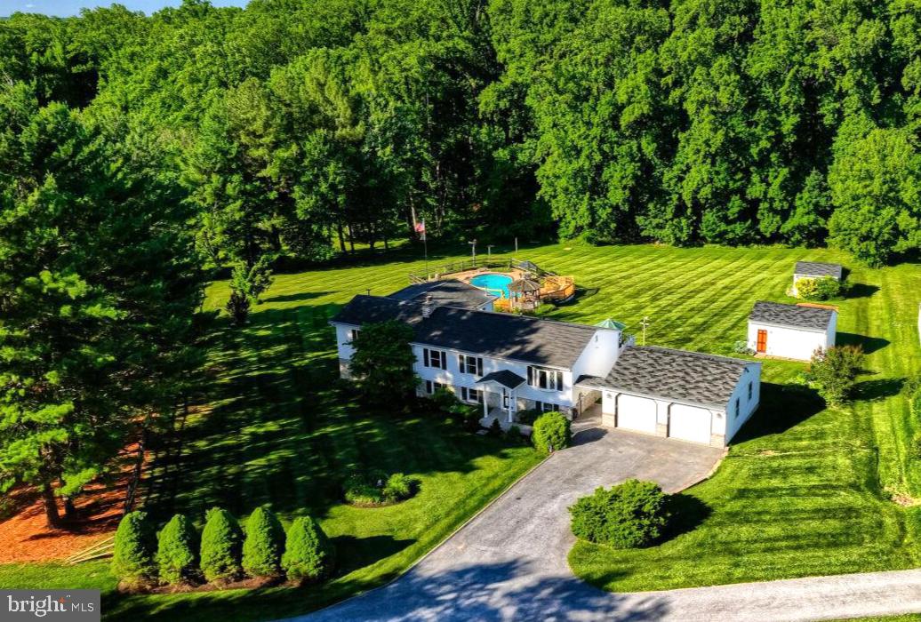 Where Country Living Meets Luxury

Nestled on a premium, rolling 2.86 acre wooded lot in the desirable Streamwood community of Sykesville, this exceptional 3-4 bedroom split foyer offers the perfect blend of privacy, comfort, and luxury.
A stunning 800-square-foot addition expands the home with an oversized owner’s suite featuring custom closets, a beautifully upgraded spa-inspired bath, and a massive recreation room designed for entertaining. The current layout includes three bedrooms and a dedicated office on the main level, while the expansive lower level serves as an impressive entertainment space, currently styled as a sports bar. The flexible floor plan allows you to tailor the home to fit your lifestyle.
The kitchen has been thoughtfully renovated, combining modern updates with character—including a charming retro refrigerator that remains fully functional.
Step outside to your private backyard retreat, complete with a custom Gunite in-ground pool, Bose speakers, engineered wood decking, and endless space for recreation. Step through the back yard woods and you will find a magical clearing with in-ground mercury vapor lights and a lovely stream and bridge.  Whether you envision corn hole, horseshoes, volleyball, gardening, or simply enjoying the peaceful surroundings, this property offers room to bring your dreams to life.
Car enthusiasts, hobbyists, and craftsmen will appreciate the oversized two-car garage with two bay doors, currently outfitted as a master carpenter’s workshop. Two additional outbuildings add even more versatility: the “Harley Shack” provides plenty of storage, and the other as a pool maintenance shed/extra storage.
With countless custom features, built-ins, and unique touches throughout, this one-of-a-kind property must be seen to be fully appreciated.