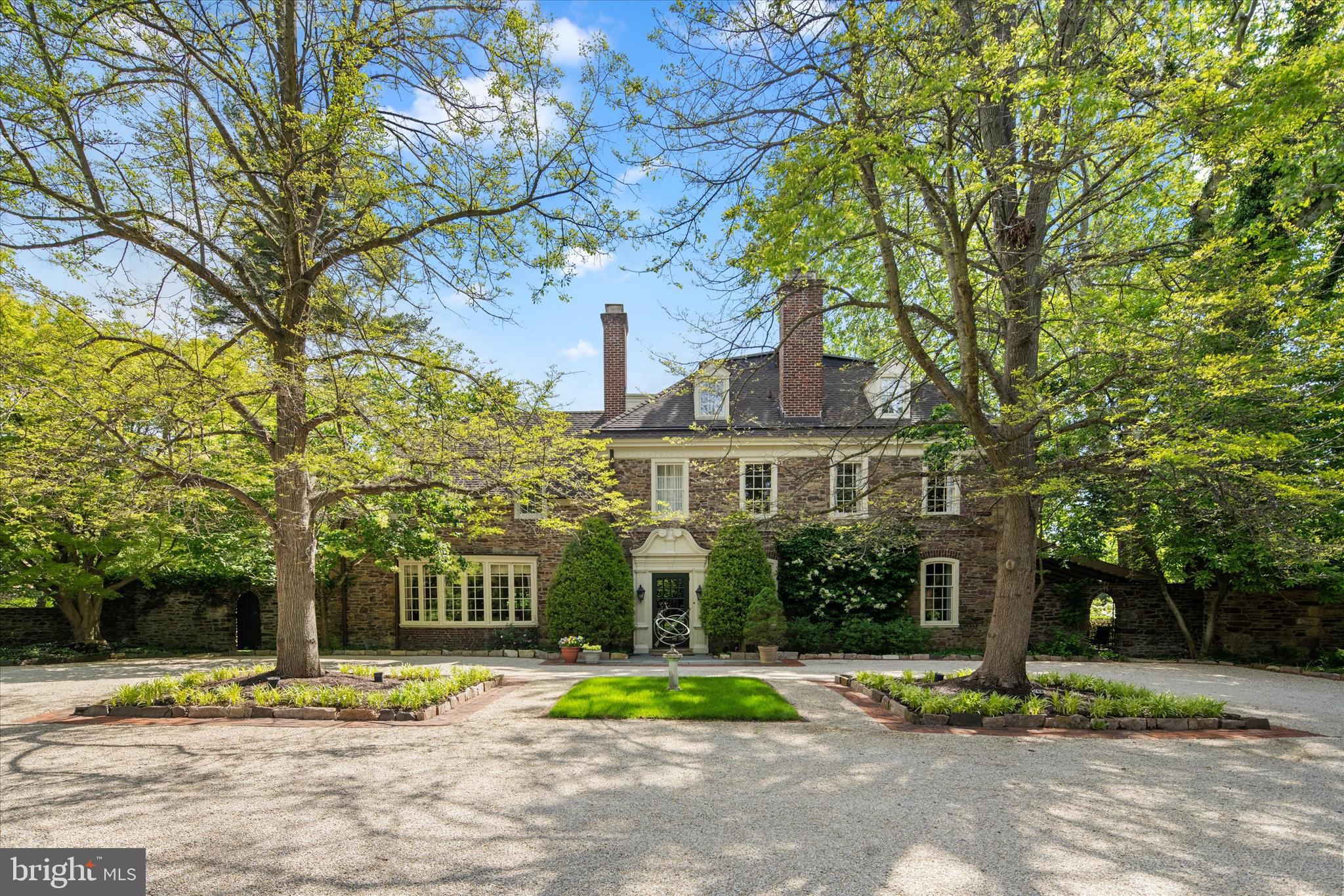 Introducing Gypsy Run, an enchanting estate nestled in the heart of Gwynedd Valley, set on over four private acres. A long, tree-lined driveway winds past a tranquil pond and reveals an impressive stone manor that exemplifies the craftsmanship and timeless elegance of a bygone era.

Steeped in history, the home showcases exquisite original details, including handcrafted Mercer tilework, wide-plank hardwood floors, deep-set windowsills, intricate millwork, arched doorways, grand crown moldings, and original stone fireplaces.

A stately Mercer-tiled foyer sets the tone, offering a gracious welcome. To the left, a formal dining room features a granite fireplace and a large bay window overlooking the motorcourt. To the right, the formal living room boasts a coffered ceiling, fireplace, and French doors opening to a sweeping slate patio. Adjoining this space is a richly paneled study with built-in shelving and a fireplace.

At the heart of the home is a sun-filled kitchen and a thoughtfully designed breakfast room addition, with floor-to-ceiling windows framing panoramic views of the grounds and pond. A large center island, professional-grade appliances, and a cozy gas fireplace create an inviting yet sophisticated space for daily living. The adjacent butler’s pantry, complete with marble countertops, a secondary dishwasher, and a beverage refrigerator, offers abundant storage and ideal support for entertaining. A rear mudroom provides access to a private two-bedroom inlaw or nanny suite.

Upstairs, the bright and expansive primary suite is a private retreat, featuring a sitting room with fireplace, a private office, a walk-in closet, and a renovated en-suite bath with a walk-in shower—plus a second, private full bathroom. A secondary suite offers comfort and privacy, while a hallway lined with closets and a laundry room leads to a third spacious bedroom with en-suite bath and walk-in closet. The third floor includes two additional bedrooms, a full hall bath, a large recreation room, and generous storage spaces.

The outdoor spaces are equally captivating. An expansive slate patio overlooks the scenic grounds, peaceful pond, and in-ground pool, surrounded by lush gardens and mature trees that lend the feel of a secluded country retreat. A charming springhouse, partially repurposed as a cabana, and a newly built three-car garage with ample additional parking complete this extraordinary property.

Ideally located just a half mile from the Gwynedd Valley train station and minutes from local shopping and dining, Gypsy Run is a rare offering—an exceptional estate that honors its historic legacy while embracing modern comfort and refined living.