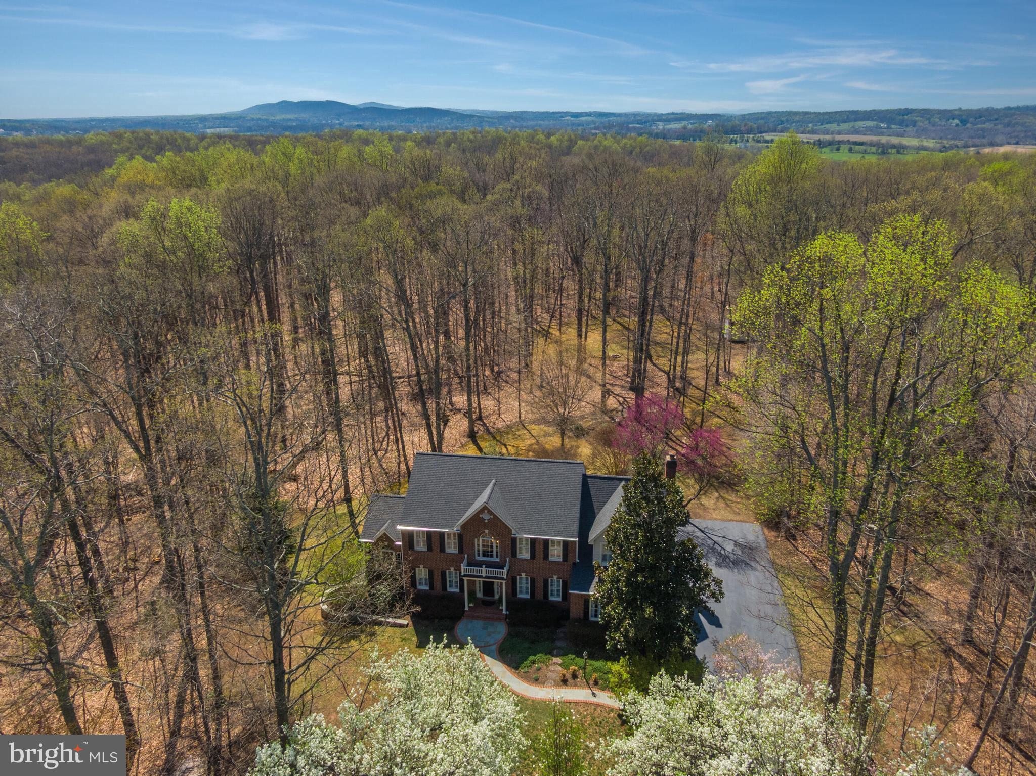 Tucked away in a storybook setting of towering trees and lush landscaping, this extraordinary estate offers the perfect balance of seclusion and convenience. Every inch of the grounds has been intentionally designed—from the meditation garden and curated plantings to a dedicated firepit area and a spacious barn for outdoor storage. A curved flagstone walkway welcomes you to the covered front porch, setting the tone for the warmth and sophistication that await inside. Step through the two-story foyer, where gleaming hardwood floors and intricate moldings create a timeless aesthetic. To the left, the formal living and dining rooms, each with French doors, seamlessly connect to a sunroom that bathes the space in natural light. The sunroom offers direct access to an intimate deck—perfect for morning coffee, quiet reflection, or stargazing. A private main-level home office, complete with built-in bookcases and cabinetry, provides an inspiring workspace.

At the heart of the home, the gourmet kitchen is a masterpiece of both style and function. Thoughtfully designed with abundant cabinetry, granite countertops, a breakfast bar, stainless steel appliances, a walk-in pantry, and a beverage center with a separate sink and refrigerator. The adjacent dine-in area opens onto an expansive Trex Transcend deck, ideal for entertaining or simply enjoying the peaceful surroundings. Flowing effortlessly into the family room, a wall of windows frames the breathtaking backyard, deck access enhances the seamless indoor-outdoor connection, while a wood-burning fireplace adds warmth and character. Nearby, the mudroom and modernized laundry area provide ample storage and direct garage access.

Upstairs, the grand primary suite is a private retreat, offering a serene sitting nook, two walk-in closets—including one exceptionally spacious with attic access—and a spa-inspired bathroom. Flooded with natural light from a skylight, the bathroom showcases a dual-sink vanity, a seamless glass shower, and a luxurious soaking tub. Three additional spacious bedrooms and a beautifully renovated hall bathroom are also located on this level. The fully finished lower level is designed for versatility, with walk-out access to a flagstone patio. A sprawling recreation room provides endless possibilities, while a dedicated space for crafts or organized storage ensures everything has its place. An additional room, ideal for a home theater or guest suite, connects to a well-appointed kitchenette with a refrigerator, dishwasher, sink, and ample cabinetry. A full, renovated bathroom enhances convenience.

Beyond the property’s serene setting, its prime location offers unparalleled convenience with the advantage of an Architectural Review Board (ARB) for neighborhood standards—without the burden of HOA dues. Less than 20 minutes to the Ashburn Metro, Dulles Airport, popular downtowns of Middleburg and Leesburg - all accessible through major commuter routes. You’re also minutes to Brambleton Town Center, Harris Teeter, Regal Movie Theater, and a variety of restaurants and shops. You will love nearby parks such as Beaverdam Reservoir, Banshee Reeks Nature Preserve, and Hal & Berni Hanson Regional Park, along with the area’s acclaimed wineries and breweries. 

Recent updates include fresh paint throughout (2025), driveway sealed (2025), new 30-year architectural roof, siding, gutters, and downspouts (2024). The kitchen boasts an updated beverage refrigerator (2024), refrigerator (2021), and dishwasher (2021). Additional improvements include new upper-level carpet and hardwoods (2021), septic pump floats (2020), a high-grade Trex Transcend deck with aluminum railing (2020), well pump (2020), sump pump (2020), whole-house filtration system (2019), bathroom remodels (2019), zone-1 HVAC unit (2019), and upgraded garage flooring (2019). The property also features an exterior generator-ready electric panel A full list of updates is available in the documents section.