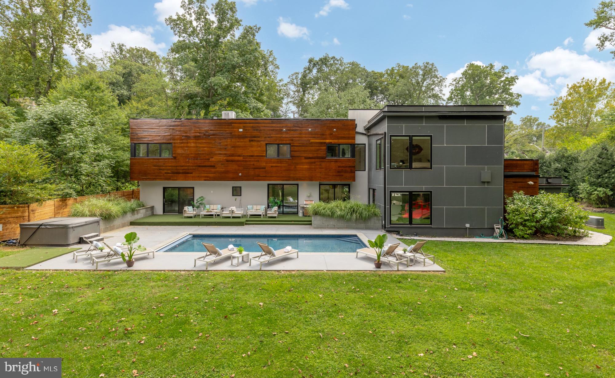 Striking modern architecture and refined luxury come together in this exceptional contemporary residence, set on over ONE ACRE of rare, private land just moments from downtown Bethesda, an extraordinarily hard-to-find combination of scale, privacy, and proximity.

Defined by clean lines, expansive windows, and warm architectural materials, the home blends modern design with its natural surroundings, creating a private retreat that feels both sophisticated and serene. Recently reimagined with a thoughtfully updated layout and beautifully renovated baths, the residence spans over 5,400 square feet of light-filled living space designed for effortless everyday living and elevated entertaining.

Inside, the home showcases rich hardwood flooring throughout the upper level and sleek modern tile on the main level, reinforcing a thoughtful balance of warmth and contemporary style. Soaring ceilings and oversized windows bring in abundant natural light while maintaining privacy throughout. Designer finishes, motorized shades, and a Savant smart-home system enhance the home’s modern functionality without sacrificing comfort.

The gourmet kitchen anchors the main living level, offering generous prep space, high-end finishes, and exceptional pantry and storage capacity—an uncommon luxury in modern homes—featuring Sub-Zero and Wolf appliances designed for both serious cooking and seamless entertaining. Open living and dining areas flow effortlessly to the outdoors, creating a layout equally suited for intimate evenings or large-scale gatherings.

The upper level features four spacious bedrooms and four beautifully updated full baths, including a luxurious primary suite designed as a true private retreat. The primary suite opens to a private balcony and features a spa-inspired bath with a soaking tub, steam shower, double vanities, a private water closet, and thoughtfully designed architectural and ambient lighting that elevates the experience from day to night. Secondary bathrooms are all well-appointed and recently redone, featuring a soaking tub and sleek tiled showers with modern finishes throughout.

The main level includes an additional bedroom and full bath, ideal for guests, an office suite, or flexible living arrangements.

Outdoors, the property unfolds into a true resort-style sanctuary. A dramatic front-entry fountain sets the tone on arrival, while the expansive rear patio, lush privacy, and stunning pool with an electronic cover create an outdoor oasis rarely found so close to downtown Bethesda. Whether hosting poolside gatherings, enjoying quiet mornings surrounded by nature, or unwinding at the end of the day, the setting offers a level of space and tranquility that is nearly impossible to replicate.

Additional highlights include a garage with a striking glass-panel door, abundant storage throughout, and a location that delivers the best of both worlds: over an acre of land with immediate access to Bethesda Row, dining, shopping, and Metro.

Why go to a hotel when you can go home.
PRIVATE RESIDENCE — BY APPOINTMENT ONLY