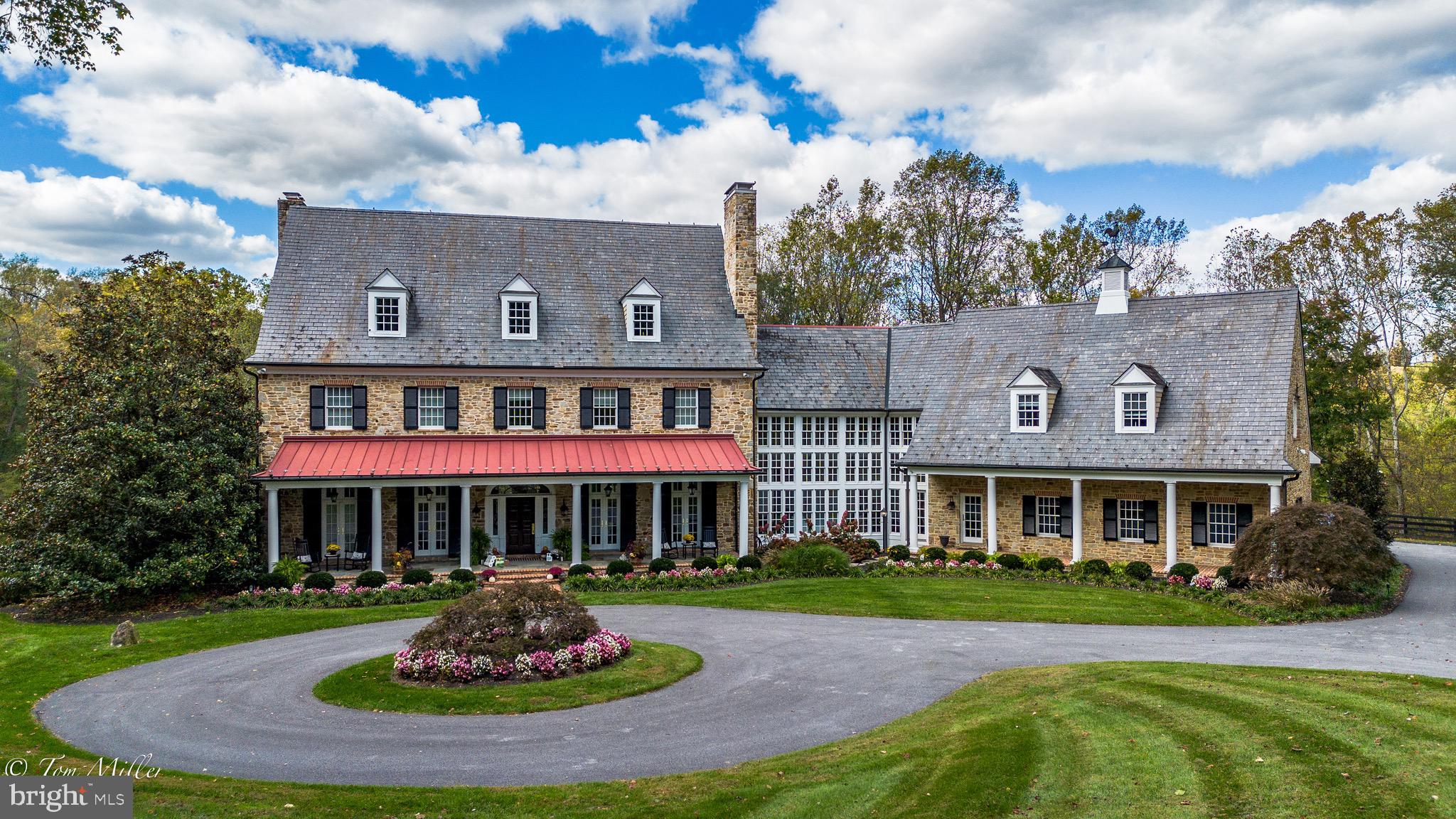 Considerable price refinement on this exquisite home in the heart of My Lady's Manor in Monkton. Don't miss your opportunity to be among the first to schedule your private showing as we enter the Spring market. Please note, when following directions as they are in the listing, it is less than 10 minutes to Hunt Valley & I-83. Nestled on nearly 13 prime acres, 1912 Corbridge Lane has been described as one of the most beautiful homes and properties in Maryland, with a design by architect Joanne Moncure, AIA and meticulously brought to life by custom home builder, Jeff Duerbeck. This remarkable Manor Home with a Butler Stone exterior and slate roof spans four levels, plenty of space to accommodate multi generational living if needed and and there is the option to add an elevator. This home was designed to combine historic charm with modern elegance & amenities in 12,000 square feet of luxurious living space. The spectacular views and stunning outdoor areas include an onsite hiking trail, a stocked pond, and over 700 feet of private frontage on the Gunpowder Falls River and the possibility of making it a farmette.
AS you enter the home, your eyes are immediately drawn to the soaring windows and the impressive wood and wrought iron spiral staircase. The Great Room offers a vaulted coffered ceiling, a Butler Stone wood burning fireplace and custom built-in cabinetry with adjacent French doors leading to a large, covered veranda. The Dining Room is the perfect place for lavish entertaining and includes a wood burning fireplace and French doors leading to a covered front porch.
The incredible Chef’s Kitchen was designed with entertaining in mind. An expansive Quartzite center island and counters, custom cabinetry, Wolf 6 burner gas range, two dishwashers, three ovens and two wood paneled refrigerators adorn this impeccable space. A Breakfast Room has a built-in banquette seating and sliders leading to a large screened in porch with scenic views. There is also a rear staircase leading to the upper levels.
The second level boasts five bedrooms including a large Primary Suite with French doors off the bedroom leading to a rear porch which offers breathtaking views of the pond and the Gunpowder. The Primary bath has Travertine flooring, an oversized jetted tub, large walk-in shower, his/her vanities, and oversized walk-in closets. Four additional spacious bedrooms including a Guest/Au Pair/In-law Suite including a living room, kitchenette,  full bathroom and its own entrance.
The lower-level Irish Pub features a Media Room, Wine Cellar, custom crafted bar, billiard room, and a walk-out leading to the pool area. The heated in-ground pool is surrounded by lush landscaping, waterfall spa, lounge areas and pavilion that provides a tranquil retreat.
Enjoy hiking, biking, fishing, kayaking, local wineries, breweries and more, all set within one of Baltimore County’s most coveted zip codes in the desirable Hereford Zone. Enjoy country living yet convenience to Hunt Valley Towne Centre and  and  I-83. This is a one-of-a-kind estate property. Please make an appointment to experience in person today!